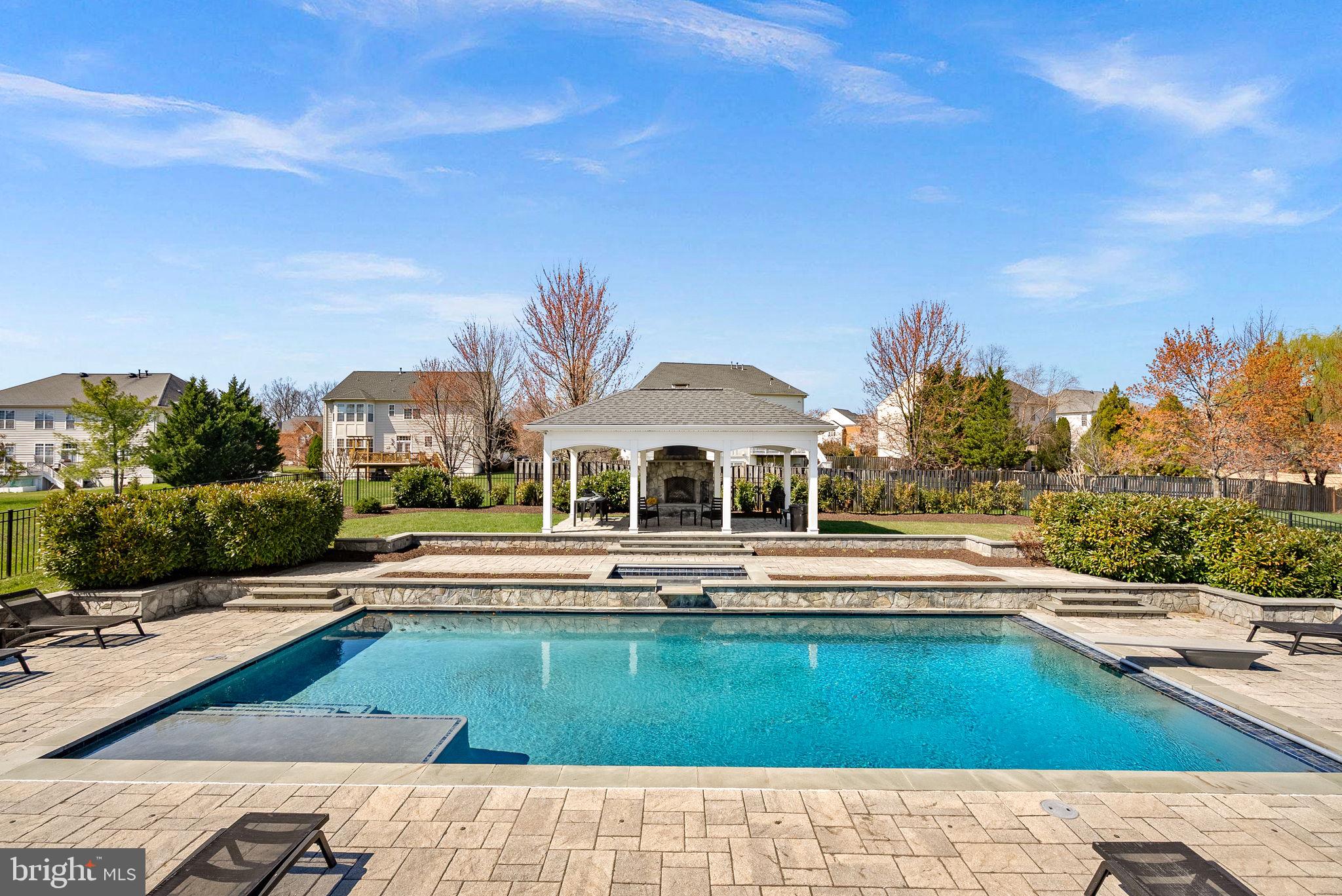 Experience unmatched luxury in the heart of Ashburn’s highly sought-after Belle Terra community! This exceptional east-facing estate offers over 6,800 finished square feet of refined living space and more than $500,000 invested in a truly resort-style backyard oasis.

Step outside and be captivated by your private retreat, featuring a custom NV Blu-built heated saltwater pool and spa, enhanced with stunning spillover and sheer descent water features, extensive hardscaping, and elegant retaining walls. Entertain year-round beneath the covered open-air pavilion, complete with a striking herringbone fireplace, or host unforgettable gatherings on the recently replaced oversized Trex deck—perfect for becoming the envy of the neighborhood.

Inside, the home continues to impress with 5 spacious bedrooms and 4.5 bathrooms upstairs, plus a main-level bedroom ideal for guests or multigenerational living. Enjoy the warmth and charm of four interior fireplaces, along with peace of mind from recent upgrades including HVAC, hot water heater, and roof.

The chef’s kitchen is designed to inspire, showcasing a 48-inch KitchenAid refrigerator/freezer, stainless steel appliances, an expansive island with a separate vegetable sink, and a beverage refrigerator—perfect for both daily living and entertaining.

The walk-out basement is truly an entertainer’s dream, offering direct pool access, a massive custom bar with ice maker, commercial-grade beer refrigerators, dishwasher, and sink. Additional highlights include a pool table/game area, a private gym or office space, and a stylishly updated full bathroom.

All of this is ideally located just minutes from the Silver Line Metro, approximately 7 miles to Dulles International Airport, and with easy access to the Dulles Greenway—making commuting effortless. Zoned for the top-rated Briar Woods High School pyramid, this home offers both luxury and convenience.

This is more than a home—it’s a lifestyle. Come claim your place as one of Belle Terra’s finest and most admired residences!
