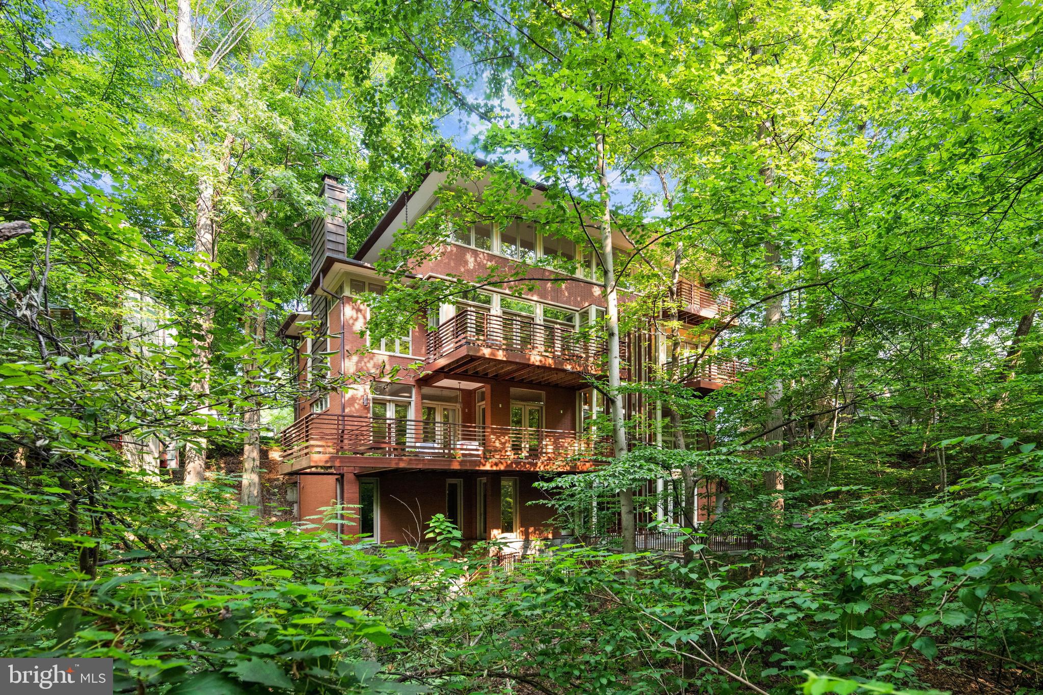 Now positioned at $3,995,000 - one of the best $/SF values in NW DC!

Designed by renowned architect Travis Price, this extraordinary contemporary residence is a rare architectural offering tucked away at the end of a quiet cul-de-sac in sought-after Forest Hills. Set on a large 0.23-acre lot among the treetops and just moments from Rock Creek Park, the home offers the unique experience of luxury living immersed in nature.

Constructed in 2004 with a striking Roman brick exterior, the residence encompasses approximately 10,000 square feet across four levels. Dramatic walls of glass, soaring ceilings, and expansive windows flood the interiors with natural light while framing breathtaking wooded vistas throughout. Highlights include 10' main level ceilings, a spectacular Living Room with approximately 20' ceilings and walkout deck, elegant Dining Room, Family Room with fireplace, and a spacious eat-in Kitchen opening to a second outdoor deck as well as the 1-car garage. An elevator services all levels. 

The private Primary Suite features its own deck, oversized walk-in closet, and spa-inspired bath, while four additional Bedrooms, 5.5 Baths, and expansive lower levels provide exceptional flexibility for entertaining, recreation, and guest accommodations. With seamless indoor-outdoor living, remarkable architectural pedigree, and an unrivaled natural setting, this is one of Forest Hills' most distinctive residences.