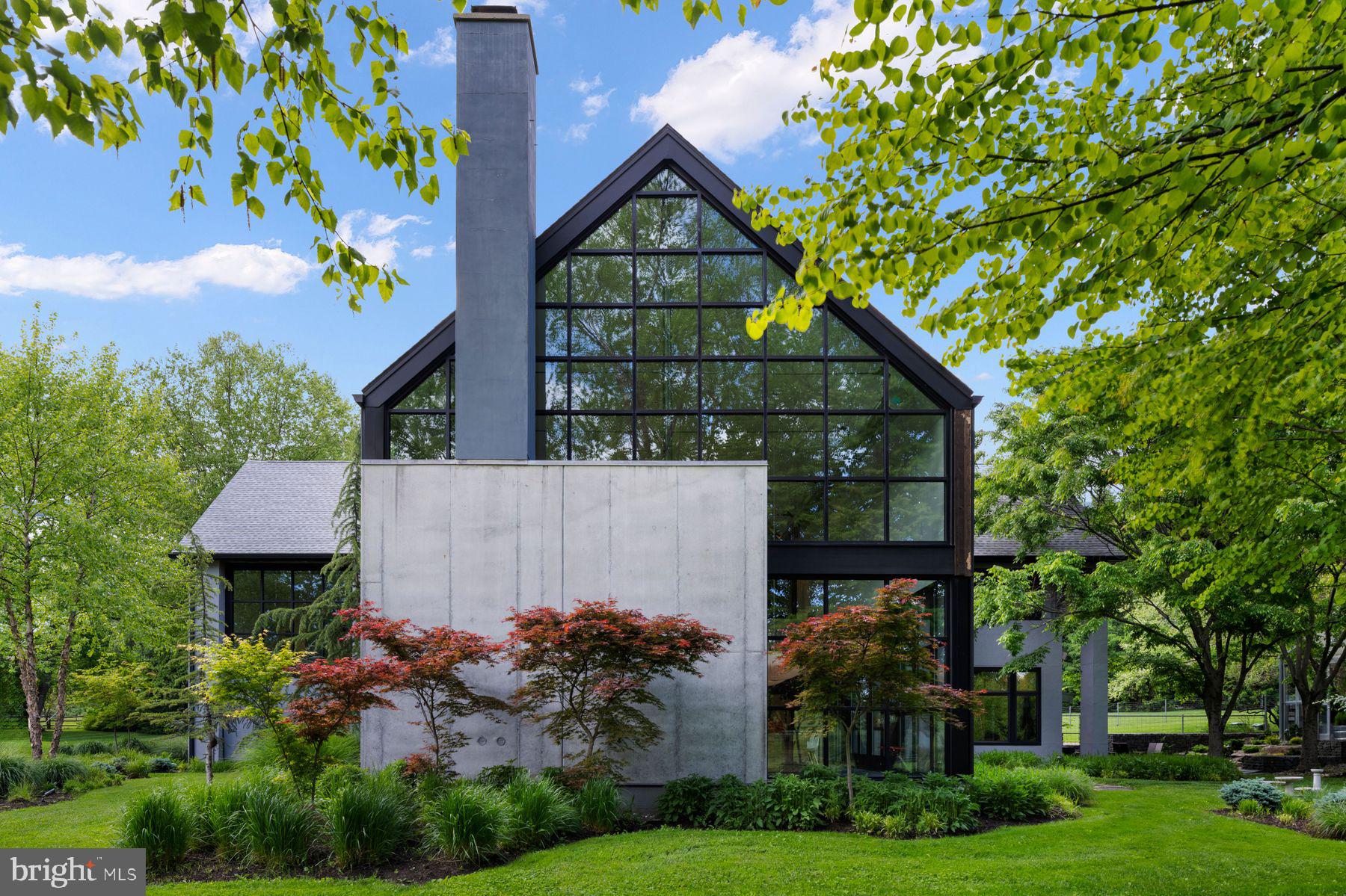 An Architectural Masterpiece — The Glass Barn Published in Architectural Record (1988) and reimagined in 2020, The Glass Barn is a landmark of modern design that marries dramatic architecture with effortless livability. Originally designed by Richard Olcott and Todd Schliemann of Polshek & Partners, this striking residence is defined by 28-foot soaring ceilings, expansive open spaces, and walls of glass that frame the surrounding landscape as living art. At the heart of the home, the great room showcases a floor-to-ceiling concrete wood-burning fireplace, polished concrete radiant-heat floors with reclaimed hardwood accents. The expansive chef’s kitchen is both functional and dramatic, with soapstone countertops, diamond-plate custom steel cabinetry, professional-grade appliances, and a seating area with a wood burning fireplace. A 1,200-bottle climate-controlled glass walled wine room completes the entertaining core. The primary suite is a sanctuary unto itself, featuring a circular glass-walled sitting room with a suspended fireplace, spa-like bath with skylit stone shower, and a boutique-like dressing room. Additional highlights of the home include a circular-walled library, a studio, office, four bedrooms, three and a half baths, a full-floor sun drenched lower level recreation room and an attached 2 car garage. Set on 6.3 acres of rolling meadow and mature trees, the property is as serene as it is private. A two-acre wildflower field with meandering paths provides a changing canvas with each season, enhanced by professional landscaping, lighting and irrigation. The resort-caliber amenities rival those of a private club: Black-bottom heated pool with sun shelf & spa, Pickleball/platform tennis court & bocce court, Heated commercial glass greenhouse; a year round grand entertaining space with seating for 20 and dual wood burning fireplaces, Expansive lawns, multiple outdoor dining areas, and a large motor court for guest parking. The Glass Barn is more than a residence — it is a published work of art, a stage for entertaining, and a retreat for ultimate privacy. An architectural icon that continues to evolve without losing its original vision.