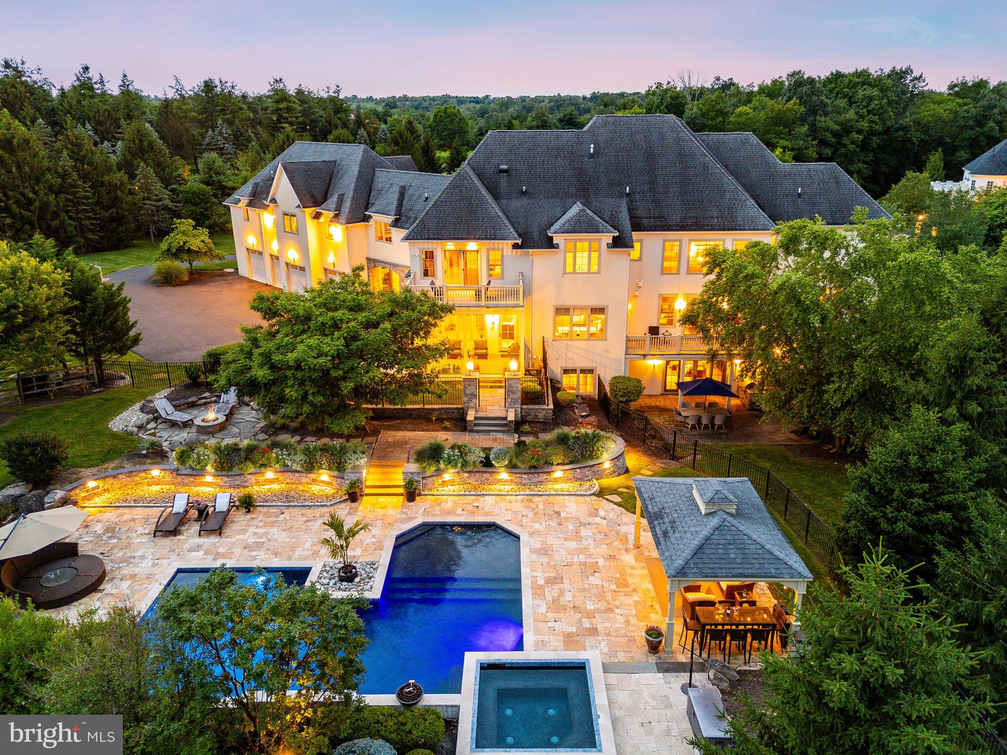 Welcome to 3 Stonebridge Crossing Road, an extraordinary estate offering privacy, elegance, and resort-style living in the heart of Newtown’s prestigious Creeks Bend community. Set on over 6 manicured acres, this custom-built residence combines timeless architectural design with modern amenities across 10,500+ square feet of refined interior space. Built by the renowned Zaveta Custom Homes and envisioned by the esteemed Ralph C. Fey Architect, this six-bedroom, nine-bathroom residence stands as a true testament to luxury and refined living. Known for their exceptional craftsmanship and attention to detail, Zaveta and Fey have created a home that exemplifies elegance and sophistication. As you arrive, a sweeping drive leads through a professionally landscaped approach to an impressive motor court and porte-cochère, framed by a stately stone and stucco façade. A pair of handcrafted double doors opens into a dramatic two-story foyer with soaring windows, a sculptural floating staircase, and designer lighting. An elevator connects all floors, ensuring ease of access throughout the home. The main level features a formal dining room with abundant natural light, ideal for both intimate dinners and grand-scale entertaining. A richly appointed study with floor-to-ceiling wood built-ins offers the perfect setting for a private home office. The open-concept kitchen is a chef’s dream, anchored by a large center island, sleek stone countertops, and top-of-the-line Miele and Thermador appliances. A butler’s pantry with glass cabinetry and a beverage station seamlessly connects to the entertaining spaces. Adjacent to the kitchen, the sunroom flows into a comfortable great room with a linear fireplace and expansive views of the backyard. A secondary lounge area with large-format tile floors and custom built-ins offers flexibility for casual living or media viewing, while an additional sitting room with two-story ceilings and oversized windows creates a serene space for conversation or reading. Upstairs, the private quarters include five spacious bedrooms, each with direct access to a full bathroom. The luxurious primary suite is a true retreat, featuring French doors opening to a private balcony overlooking the grounds, a spa-style bath with an oversized soaking tub, dual vanities, custom storage, and generous closet space. The finished lower level is designed for elevated recreation and relaxation. It includes a stylish great room with a modern fireplace, a full wet bar with custom wine display, an additional office or executive workspace, a fitness room, and a playroom—all finished with high-end materials and thoughtful design. Outside, the estate transforms into a personal resort. The expansive backyard is centered around a beautifully designed pool with spa, water features, and an integrated sun shelf for lounging. A covered pavilion offers an elegant space for outdoor relaxation, while the built-in kitchen with stainless grill is ready for alfresco dining and weekend gatherings. A stone fire pit, multiple patio areas, and lush green lawns offer plenty of room for entertaining or unwinding. The grounds also include raised garden beds, a fenced play area, and carefully curated plantings for year-round beauty and privacy. Additional highlights include a spacious mudroom, four-car garage, recessed lighting throughout, wide-plank hardwood flooring, and multiple zones for heating and cooling. Every inch of this home has been thoughtfully crafted with the highest standards in mind. Located within the top-rated Council Rock School District and just minutes from Newtown Borough’s charming shops, dining, and cultural attractions, this is a rare opportunity to own one of Bucks County’s most exceptional homes. 3 Stonebridge Crossing Road is more than a residence, it’s a lifestyle.