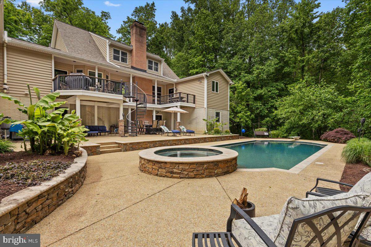 Over 5,000 finished square feet of luxury living featuring a chef’s kitchen with a premium Wolf stove, a heated saltwater pool with spa, and exceptional spaces for entertainment, all nestled in a private, wooded setting less than an hour from Washington, D.C. and Annapolis. The impressive kitchen is the heart of the home, offering a premium Wolf stove, abundant workspace, and an open layout that flows seamlessly into the main living areas, where soaring vaulted ceilings, refinished hardwood flooring, custom built-ins, carved wood ceilings, and a cozy fireplace showcase the home’s quality craftsmanship and timeless design. The main level offers a spacious primary suite with a full bath, plus an additional full bath for guests. Upstairs are three additional bedrooms, including a private en-suite and a charming bedroom with a hand-painted forest mural. Need flexible living space? The finished detached garage includes a dedicated studio/workspace and a private guest suite with a bedroom, full bath, and separate work area—perfect for extended family, overnight guests, a home office, or creative pursuits. The recently finished lower level adds even more versatility with a bedroom, expansive recreation or fitness room, and a half bath with direct access to the backyard. Outside, your private retreat awaits with a 4-year-old heated saltwater pool featuring a PebbleTec finish, built-in spa, color-changing lighting, and extensive landscape lighting that creates a spectacular setting for evening entertaining. Ample parking and a large storage building add everyday convenience. Meticulously maintained and thoughtfully updated throughout, this one-of-a-kind property offers the perfect blend of luxury, privacy, versatility, and convenience.