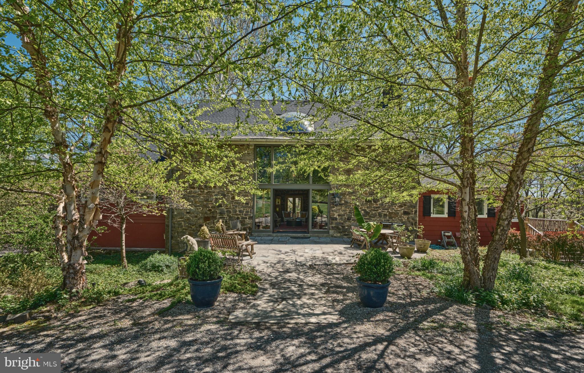 Set on 4.42 private acres in the heart of Solebury, Stonecroft is a storied Bucks County estate with origins dating back to an early Penn grant. Originally constructed by the Ely family in the late eighteenth century as a stone bank barn, Stonecroft was then converted to the studio of noted New Hope Impressionist Stanley Reckless, and, most recently, thoughtfully transformed into a one-of-a-kind private residence. Stonecroft is currently owned by the producing director of Bucks County Playhouse, where countless stage luminaries were house guests. 
A long, private drive lined with mature hydrangeas leads to a setting defined by rolling lawns, specimen trees, and complete privacy. Rich in history and artistic legacy, the home retains its original character—exposed stone walls, massive beams, and timeless architectural scale—while incorporating meaningful updates for modern living throughout its history.
The centerpiece of the home is the magnificent main stone great room, measuring approximately 40’ x 28’, featuring soaring ceilings, dramatic volume, and radiant heated barn wood floors. The recently updated kitchen also offers radiant heat and opens to a charming screened-in porch—ideal for casual dining and evening entertaining.
The main residence includes 4 bedrooms and 3.5 baths, with multiple living spaces that balance historic character and contemorary functionality.
Outdoors, the property unfolds as a private compound. A large pool is surrounded by mature butterfly bushes and serviced by a cabana with bar and refrigerator—designed for effortless summer living. To the rear, the property sweeps down to a natural pond and lush wall of bamboo that borders a 166 acre park. Within the park sits Lake Solebury, a gorgeous 70 acre lake on the site of the former New Hope quarry.  A tree-covered berm offers a rare combination of privacy and preserved surroundings.
Additional features include a detached two-car garage with guest apartment above, a substantial 40x80 pole barn, and expansive open acreage suitable for recreation, gardening, or creative use.
A rare opportunity to own a true Bucks County legacy property—where history, architecture, and setting converge in a way that cannot be recreated.