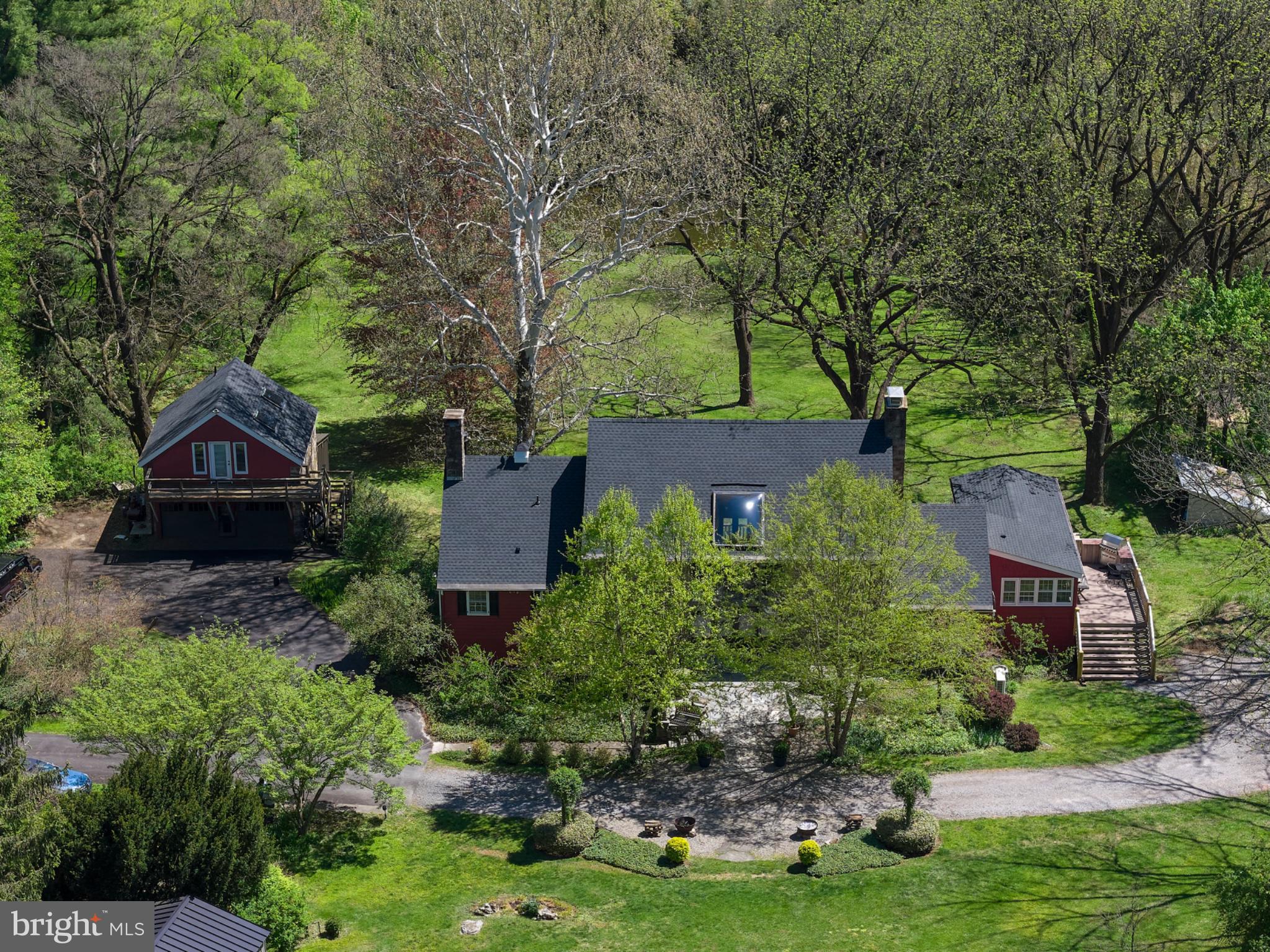 Set on 4.42 private acres in the heart of Solebury, Stonecroft is a storied Bucks County estate with origins dating back to an early Penn grant. Originally constructed by the Ely family in the late eighteenth century as a stone bank barn, Stonecroft was then converted to the studio of noted New Hope Impressionist Stanley Reckless, and, most recently, thoughtfully transformed into a one-of-a-kind private residence. Stonecroft is currently owned by the producing director of Bucks County Playhouse, where countless stage luminaries were house guests. 
A long, private drive lined with mature hydrangeas leads to a setting defined by rolling lawns, specimen trees, and complete privacy. Rich in history and artistic legacy, the home retains its original character—exposed stone walls, massive beams, and timeless architectural scale—while incorporating meaningful updates for modern living throughout its history.
The centerpiece of the home is the magnificent main stone great room, measuring approximately 40’ x 28’, featuring soaring ceilings, dramatic volume, and radiant heated barn wood floors. The recently updated kitchen also offers radiant heat and opens to a charming screened-in porch—ideal for casual dining and evening entertaining.
The main residence includes 4 bedrooms and 3.5 baths, with multiple living spaces that balance historic character and contemorary functionality.
Outdoors, the property unfolds as a private compound. A large pool is surrounded by mature butterfly bushes and serviced by a cabana with bar and refrigerator—designed for effortless summer living. To the rear, the property sweeps down to a natural pond and lush wall of bamboo that borders a 166 acre park. Within the park sits Lake Solebury, a gorgeous 70 acre lake on the site of the former New Hope quarry.  A tree-covered berm offers a rare combination of privacy and preserved surroundings.
Additional features include a detached two-car garage with guest apartment above, a substantial 40x80 pole barn, and expansive open acreage suitable for recreation, gardening, or creative use.
A rare opportunity to own a true Bucks County legacy property—where history, architecture, and setting converge in a way that cannot be recreated.