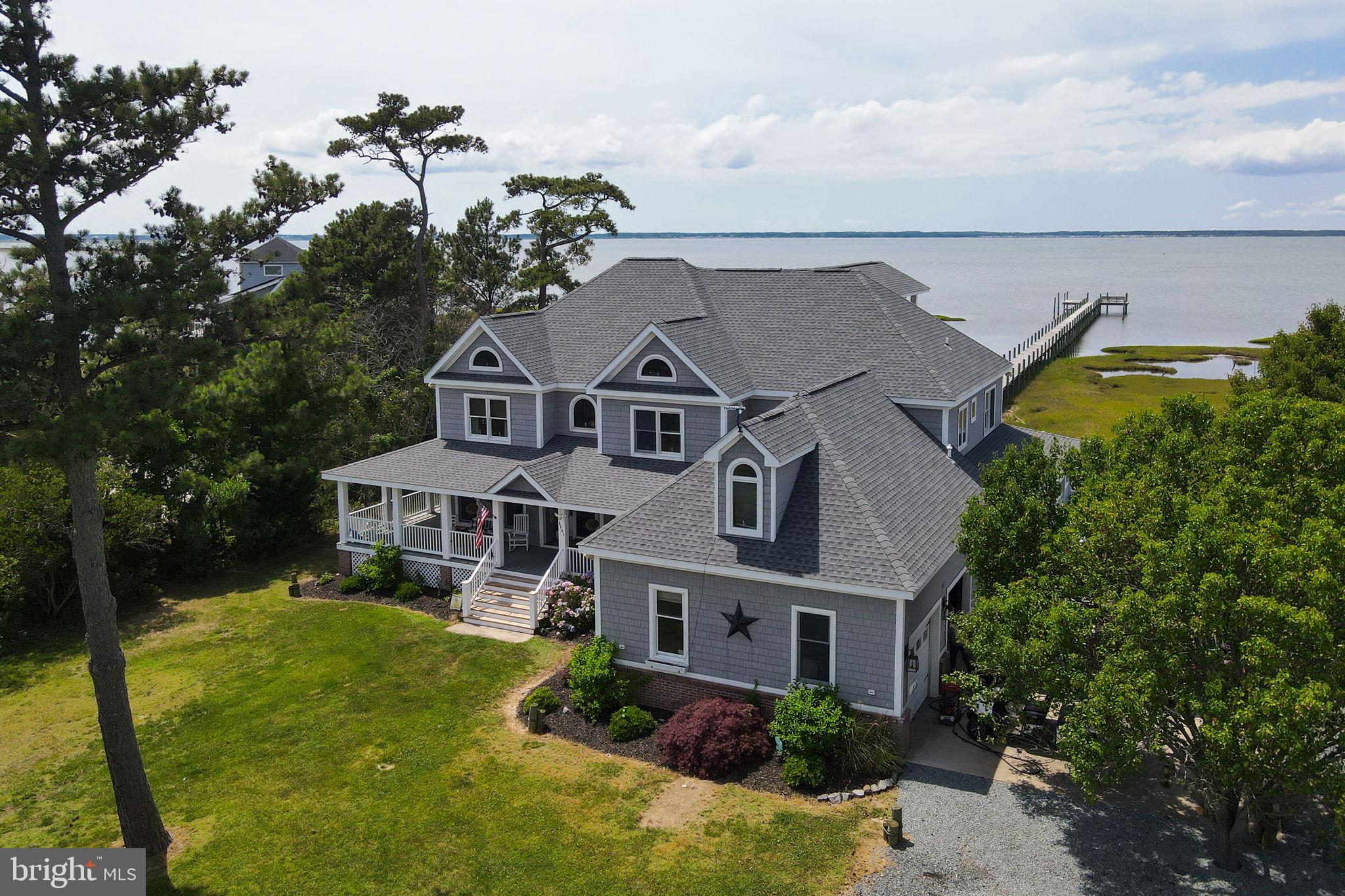 Experience exceptional waterfront living at this stunning Chincoteague Bay retreat, where panoramic bay views, spectacular sunsets, expansive outdoor living spaces, and an impressive private pier create the ultimate Eastern Shore lifestyle. Situated on a private waterfront setting, this remarkable property offers 5 bedrooms, 4.5 baths, over 4,000 square feet of living space, and a floor plan designed to maximize both comfort and breathtaking water views.

A welcoming wrap-around porch sets the tone as you arrive, providing the perfect place to relax, entertain, and enjoy the coastal breeze. Inside, walls of windows frame sweeping views of Chincoteague Bay while beautiful hardwood floors, custom wood trim, solid wood doors, and extensive custom cabinetry showcase the home's quality craftsmanship. Throughout the home, thoughtful details reflect the property's coastal setting, including an original hand-painted mural by renowned Chincoteague artist Tracy Taylor featured in one of the guest bedrooms. The first floor offers a spacious family room with fireplace, a separate living room, a flexible office/den space, a full guest bathroom, and generous dining areas designed for both everyday living and entertaining.

The well-appointed kitchen offers abundant cabinetry, a pantry, and seamless flow into the dining and living areas, making it ideal for both everyday living and entertaining. Nearly every gathering space is positioned to take advantage of the home's exceptional waterfront setting.

The second floor features four bedrooms, including a luxurious waterfront primary suite with a vaulted ceiling, an expansive private balcony overlooking the bay, a massive walk-in closet, and a spa-inspired bath featuring a double vanity, soaking tub, separate tiled shower, and extensive custom cabinetry. Three additional guest bedrooms, a full hall bath, and a conveniently located laundry room complete the second level.

The third floor serves as a private retreat featuring the fifth bedroom suite with its own full bath, walk-in closet, private waterfront balcony, and panoramic views across Chincoteague Bay. This level also provides access to substantial attic storage space.

The outdoor amenities are truly exceptional. Enjoy multiple waterfront balconies, the expansive wrap-around porch, and a waterfront patio with fire pit overlooking the bay. A substantial private pier extends through the marsh to open water and features multiple docking areas with room for several boats, expansive sunning and swimming platforms, and endless opportunities for boating, fishing, crabbing, kayaking, paddleboarding, and entertaining on the water. From the home, porch, balconies, patio, and pier, enjoy breathtaking sunset views across Chincoteague Bay.

Additional features include an attached 2-car garage with extra storage space, extensive attic storage, two storage sheds, and a large parking area for guests, boats, and recreational equipment.

Rarely does a property combine this level of privacy, panoramic waterfront views, abundant living space, exceptional boating amenities, and spectacular sunset vistas. This is a truly remarkable opportunity to own one of Chincoteague's premier waterfront properties.

 Roof was replaced five years ago, first floor HVAC was replaced 2025 with a heat pump w/ propane pack, second floor HVAC was replaced a couple of years ago.