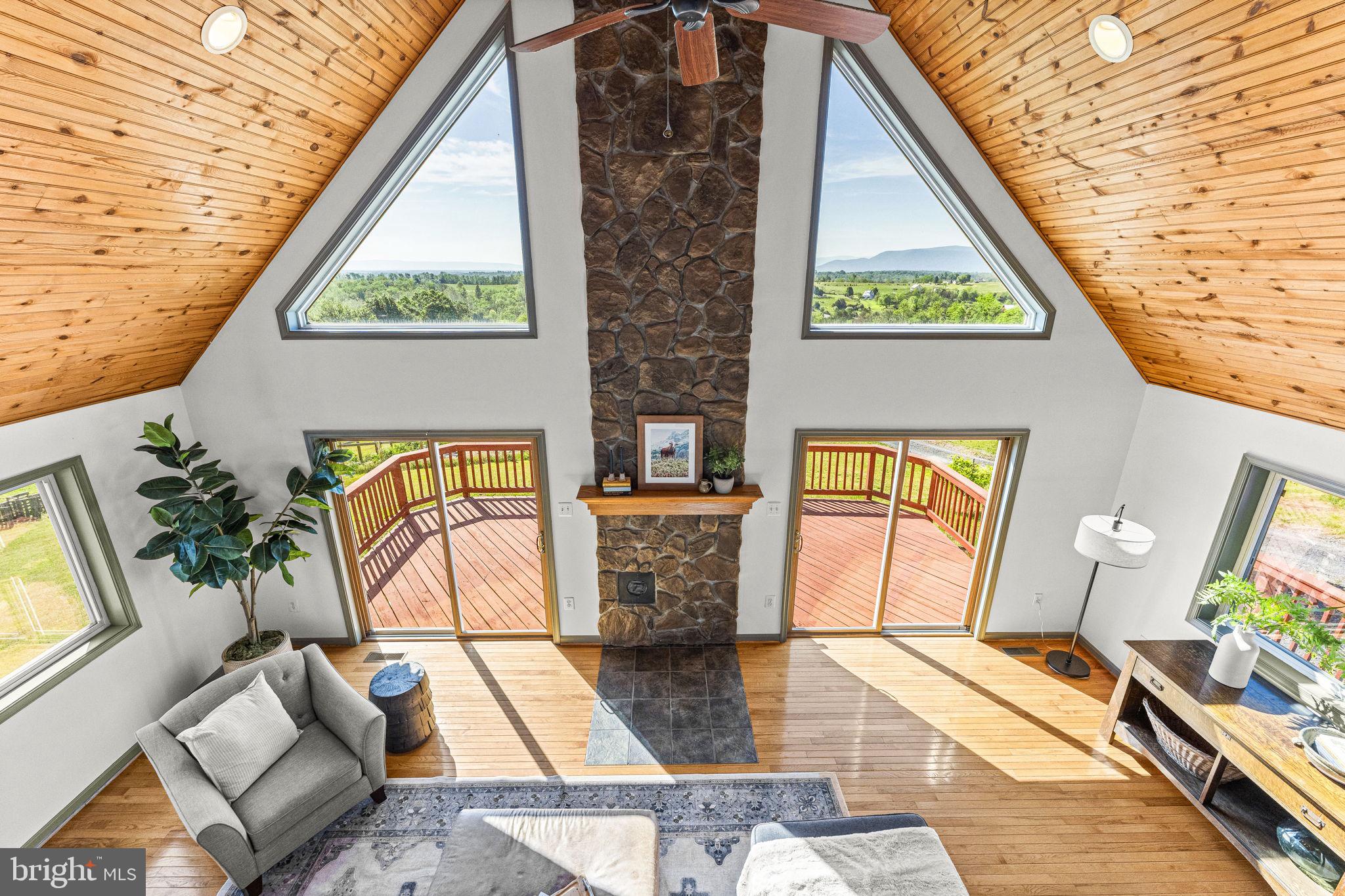 Set against sweeping Blue Ridge Mountain views, this 5-acre retreat offers the opportunity to live a more intentional, inspired lifestyle — whether as a spacious 5-bedroom, 3.5 bath family home, a thriving homestead with income-producing Airbnb, or peaceful weekend retreat for creatives and nature lovers alike. Whatever the vision, it can be realized here.
Built in 2004, the home welcomes morning light and ends each day against mountains illuminated by twilight. Inside, the details are deliberate and well-crafted, creating a balance of warmth, openness, and everyday functionality. 
Enter into the Great Room, where a soaring pine-finished vaulted ceiling and dramatic wall of windows create a warm, light-filled gathering space. The dining area flows into the well-appointed kitchen, featuring granite countertops, premium locally-made cabinetry, a large island with seating, coffee bar, oversized pantry, and adjacent laundry room.  
The spacious main-level primary suite is privately positioned to capture sunrise views and features an updated ensuite bath, enormous walk-in closet, and additional second closet.
Upstairs are 3 generously sized bedrooms and a full bath. Multiple walk-in closets, oversized windows that frame valley views and fill the rooms with natural light, and a charming reading nook overlooking the living room below all enhance this level.
The lower level continues the home’s remarkable flexibility, offering a fully separate living space with 1 bedroom, 1 bath, living room, and kitchenette. Currently operating as a successful 5-star rated Airbnb, this area could serve as multigenerational living or an au pair suite. High-speed fiber optic connectivity also supports a homeschool space, or office, complete with its own exterior entrance.
At the rear of the lower level is a large pottery studio featuring new wide-plank neutral LVP flooring. Ideal for artistic pursuits, it could easily transition into a yoga studio, gym, office, or additional flex space.  A large unfinished storage area completes this level.
Outside, every seed, plant, and tree has been planted with long-term stewardship in mind, designed to nourish, sustain, and grow more beautiful with time.  The 4,200-square-foot fenced garden follows permaculture principles that mimic nature and support regenerative practices. Curved planting beds naturally slow and absorb rainfall into the soil. Wander the mulched pathways to harvest fresh vegetables, fruits, culinary herbs, medicinal plants, and perennial flowers, all cultivated without pesticides since 2022. Beyond the garden lies an orchard planted, while a winding path leads to a tucked-away clearing ideal for a tent, yurt, or quiet evening beneath the stars.
Located just 7 miles from historic Strasburg and 90 minutes from Washington DC, the property offers both retreat and accessibility. Enjoy easy access to hiking in Shenandoah National Park, the Shenandoah River, local wineries, farm markets, and the charm of the Shenandoah Valley lifestyle.