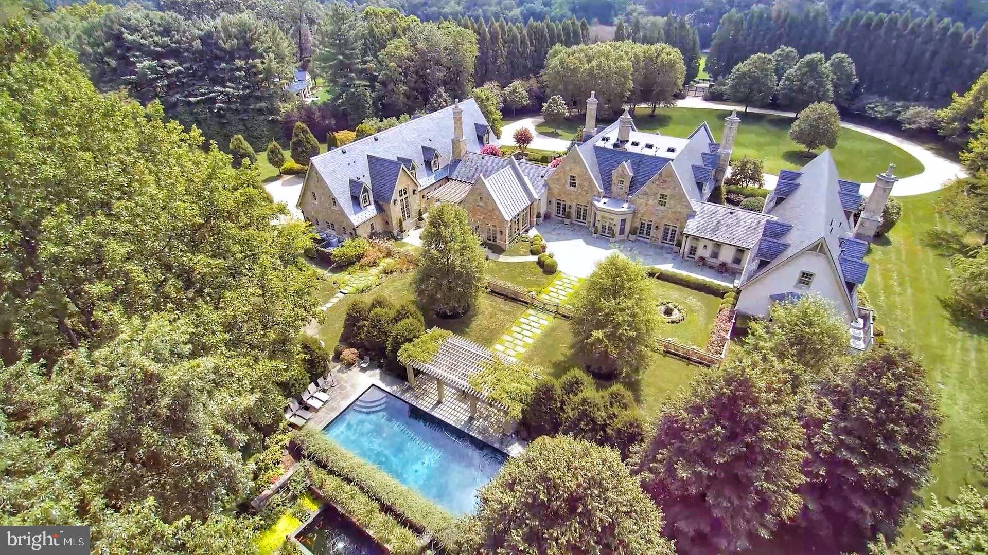 Inspired by the finest traditions of English architecture & design welcome to Alderley a magnificent, gated Cotswold Stone Manor in the heart of Great Falls on 5 private acres that are meticulously landscaped! This stunning residence captures the finest elements & amenities ideally suited for today's modern lifestyle w/ unparalleled finishes throughout the over 20,000 square feet of living space, perfect for grand entertaining or family living. This marvel of English architecture was designed by David Cooper of ACG Architects & built by BOWA Design/Build. The enchanting landscape design by Andy Balderson of Donovan, Feola, Balderson & Associates w/ Kitchen & Woodland Gardens by Sisson Landscapes includes beautifully manicured lawns, mature trees  English-style gardens. In the tradition of historic English Manor houses, this residence has an aura of timeless, stately bearing and refined elegance which is carried seamlessly from the exterior architecture throughout all of the interior spaces to create a cohesive and artful integration. Located in close-in Great Falls a short stroll or golf cart near the village down a lavender lined driveway you arrive at Alderley on sought after Innsbruck Avenue. The entire perimeter of the property is protected by an 8-foot fence set within a continuous wall of evergreens reaching heights over 40 feet, providing security & absolute privacy. This most amazing property has custom made mahogany Artistic Windows w/ simulated divided light & 99% UV filter, exquisite moldings throughout, custom mantles w/ marble hearths, artisan-designed millwork, custom cabinets & bookcases. Interior doors are all solid mahogany & door hardware is by E.R. Butler & Co. of New York. Floors on the Main and Upper Levels are random width (5  to 9 ) reclaimed antique oak. New Kitchen and Breakfast Room addition is designed and built by the original architect and builder. The design fully integrates & enhances the original plan includes exposed beams, stone accent wall, 2 Islands with solid mahogany countertops, top-of-the-line appliances including custom Lacanche Range and French Doors to outside Terraces! Main Level Master Retreat has two entryways through the Sitting Room with intricate built-in bookcases and private access to the front and rear gardens.  The suite is complete with two separate His and Her dressing wings each with custom furniture quality built-in closets and Bathrooms. The Main Level also includes Living Room with fireplace and gas logs, Dining Room has fireplace with gas logs and glass door to side garden, Library with custom shelving on every wall and access to one of the front gardens, Family Room off Kitchen with 3 French Doors to easily enjoy the Terrace with Outdoor Kitchen and Fire Pit, His Office with beamed 2-story ceiling, two walls of built-in bookcases and a balcony above that connects to the upstairs Gallery and Her Office with charming bookcases and closet with built-in bureau and cabinets. The Upper Level has four bedrooms and three full Baths that have Waterworks fixtures and Lagos Azul Limestone. Lower Level includes a stunning climate-controlled Wine Cellar has a sound system, seating area, work area and accommodations for a substantial collection of single bottles & cases of wine, dramatic Gallery Hall to Theater w/ 4 tiers of seating with 12 expansive leather reclining chairs and Projection equipment, Gym with walls of glass that opens to a sheltered patio, Spa Bath w/ walk-in shower & Powder Room. The tranquil backyard with expansive Terraces and Gardens has outdoor Kitchen, Dining Area under lovely Pergola, Rose Garden, Pool with a fountain with Pergola for al fresco entertaining, deep Koi Pond & gorgeous Gardens! The property has lawn irrigation and is self-sustaining with well, septic, whole house Generator and Security with Camera Surveillance at the Gate. The Alderley Estate is unmistakably one of the premier properties in the entire Mid-Atlantic Region!