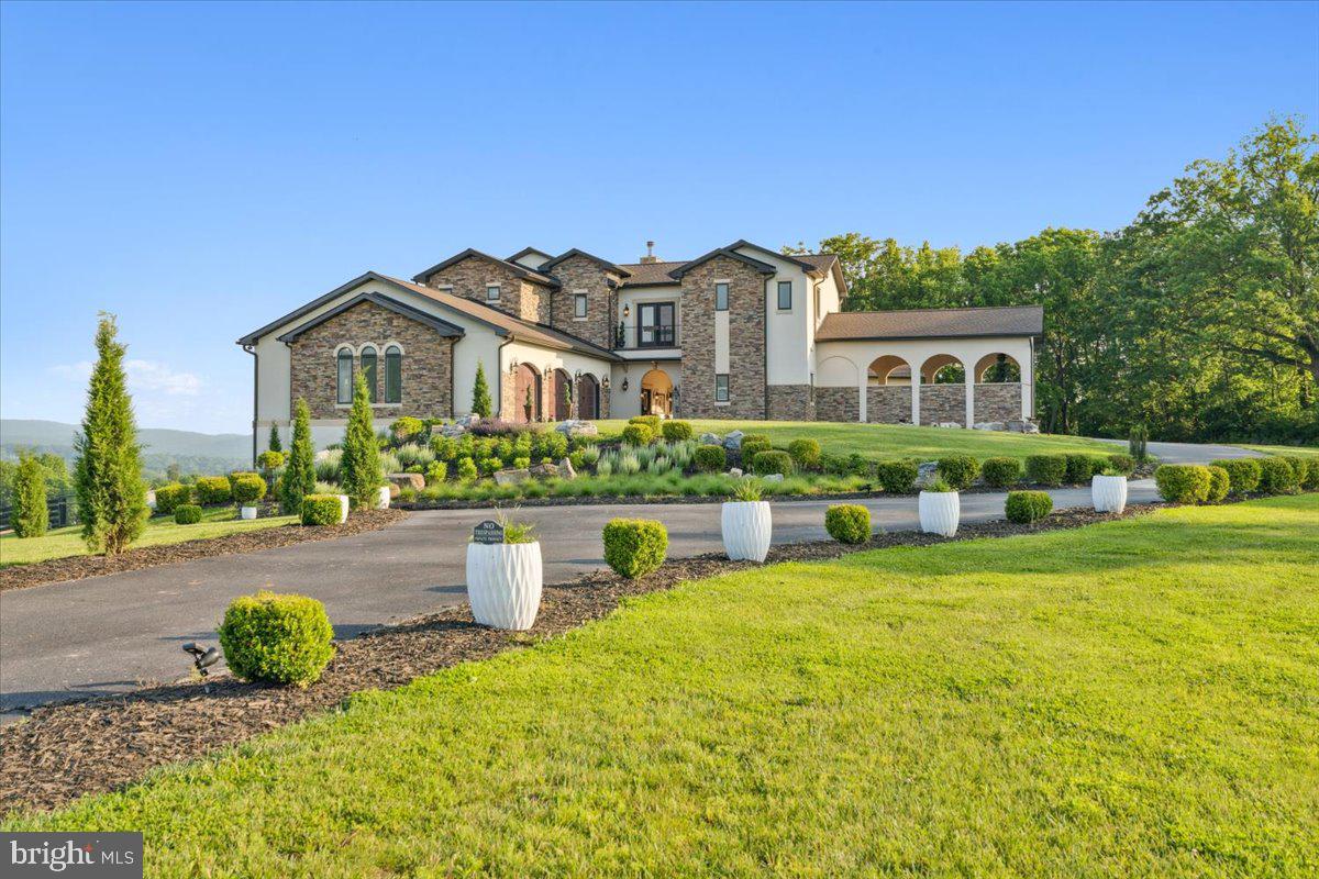 This may be the most amazing home in the Mid-Atlantic. This home is located on over 27 acres with extensive hardscaping and a luxury villa design unlike any other.  The main level includes panoramic views of this estate with custom hardwoods, a historic fireplace, coffered ceilings, a full home sound system, and a one-of-a-kind dining area that includes a balcony and endless entertainment.   All of this is accompanied by a main level primary suite that rivals any vacation getaway that you could hope for.  The upper level brings multiple balconies that provide the opportunity for escape and privacy.   Each bedroom includes a hotel style feel that is completely unique.  All bathrooms are customized and the bedrooms include expansive closets. 
The lower level is unlike any basement you have ever seen.  Over 10-foot ceilings, and a commercial equipped bar this feels like an event venue in your own home.  The style and design must be experienced in person.  Walkout access provides tons of natural light with a Northern Virginia Vineyard feel.  This estate could entertain large parties or could just be your own private oasis that allows you to escape the hustle and bustle of life.  With Geothermal heating this home is extremely energy efficient without the expenses you would expect to find in a home this size.  There is so much to take in here but don't forget to experience the hydroponic growing room underground that is currently growing vegetables for perfect off the grid living.  
If this inside is not enough the exterior offers multiple living areas, all with their own unique and spectacular views.  The attached guest house offers a bedroom, full bath, and the perfect kitchenette.  This home screams ENTERTAIN HERE!  The main level garage includes three oversized bays that extend extra deep in this garage.  The lower level garage includes more motorized storage plus a large workshop.  The property includes extensive hardscape, sprinkler systems, fenced areas and a large farmable area.  This provides the opportunity for Ag tax credit is desired.  Enjoy a wooded portion with a historic stone wall.  
Views of mountains (check), woods (check)... You will find no other home to match this in the DMV or anywhere in the Mid Atlantic Region.