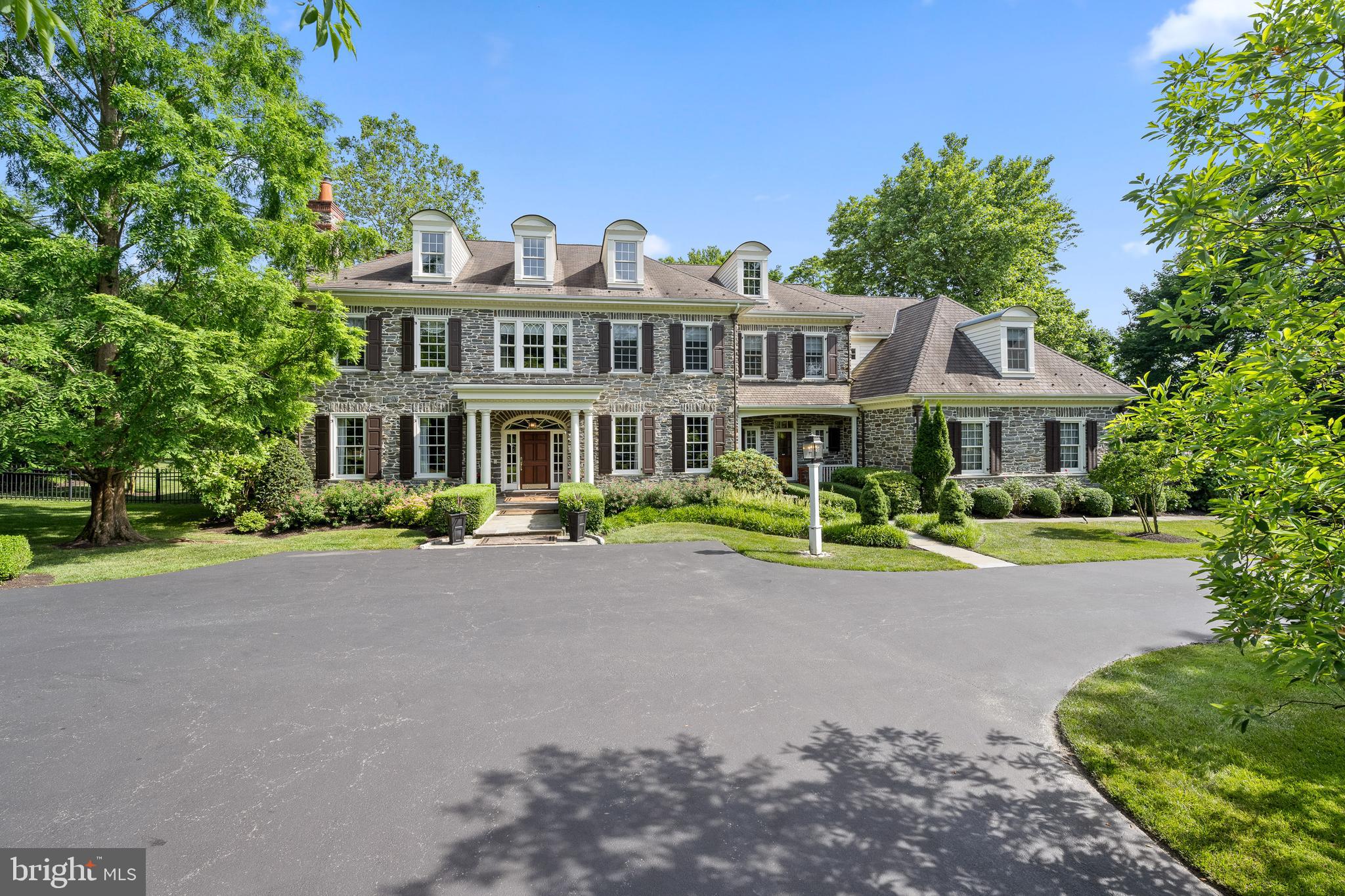 Welcome to 3 College Ave, an exquisite estate manor home in the heart of the Main Line. Originally a model home, this residence showcases unparalleled craftsmanship and attention to detail. Built by Manchester Hall Builders with renowned Lancaster County craftsmen. Meticulously maintained or upgraded by local family-owned businesses, this home remains in showcase condition. Entrance piers and estate fencing greet you as you approach the property. Positioned well back from the road, the home is screened by mature trees for complete privacy. A front motor court offers abundant parking. Entering through the marble-floored foyer, you are greeted by a grand front-to-rear center hall. The living room, with its coffered ceiling and gas fireplace, provides an inviting retreat. The dining room features two ceiling medallions and decorative moldings, served by a butler's pantry with a second dishwasher and beverage fridge. French doors from the center hall lead to a covered terrace with a built-in gas grill and fire pit, ideal for summer BBQs and fall gatherings. Extensive outdoor living spaces ensure enjoyment of the beautiful surroundings in every season. The spacious gourmet kitchen is a culinary dream. Appointed with a triple-tiered center island, granite countertops, double Thermador wall ovens, Sub-Zero refrigerator, and Thermador cooktop, the kitchen is both beautiful and functional. A large walk-in pantry offers ample storage. The breakfast room, featuring a vaulted ceiling and 3 walls of large windows, is bathed in natural sunlight. Adjacent to the kitchen, the family room boasts a coffered ceiling with patterned tin ceiling tiles. A fireplace with a floor-to-ceiling stone surround serves as the room's focal point, flanked by custom built-in cabinetry. The room also features a custom built-in wet bar. Glass-paneled doors open into the sunroom, seamlessly connecting the two spaces. The sunroom, with a gas fireplace, radiant heated slate flooring, and wood ceiling, also opens onto the covered terrace. Two conveniently located powder rooms provide easy access. Additional features on the first floor include a cherry-paneled home office/library with built-in bookcase and a gas fireplace, a workstation command center, and a mudroom leading to a heated and air-conditioned three-car garage with a dog shower. Upstairs, the primary bedroom suite is a private sanctuary with high ceilings, a sitting area, and hardwood flooring. The primary bathroom includes a tub, his and her vanities/sinks, a double-sided shower, and a large walk-in closet with built-in cabinetry and a center island. The second floor also has an en-suite bedroom, two additional bedrooms sharing a Jack and Jill bath, a second-floor laundry room, and a large bedroom with a private bath and sitting area, accessible via rear stairs. All rooms are extraordinarily spacious, with high ceilings and brightened by sunlight, offering breathtaking views of the grounds.  Plumbing rough-in on the unfinished third floor offers potential for customization, with access provided by a dedicated staircase. The finished lower level is a haven for entertainment and relaxation, including a billiards area, den, exercise area, 1000-bottle custom temperature-controlled wine cellar, and walk-out access to the beautifully landscaped rear grounds. Surround sound systems, both inside and outside, enhance the ambiance for gatherings or family evenings at home. The adjacent separately deeded lot at 5 College Ave is also available and provides 1.6 acres of additional privacy. It currently has raised bed vegetable and flower gardens, provides space for a tennis court or pool, and accommodates valet parking for up to 30 cars. Utilities are already run underground, making it a seamless addition to the property. This home stands out as the "Best of the Best" the Main Line has to offer. Superior quality construction and spectacular finishes offer a luxurious and comfortable lifestyle.  Taxes are under appeal.