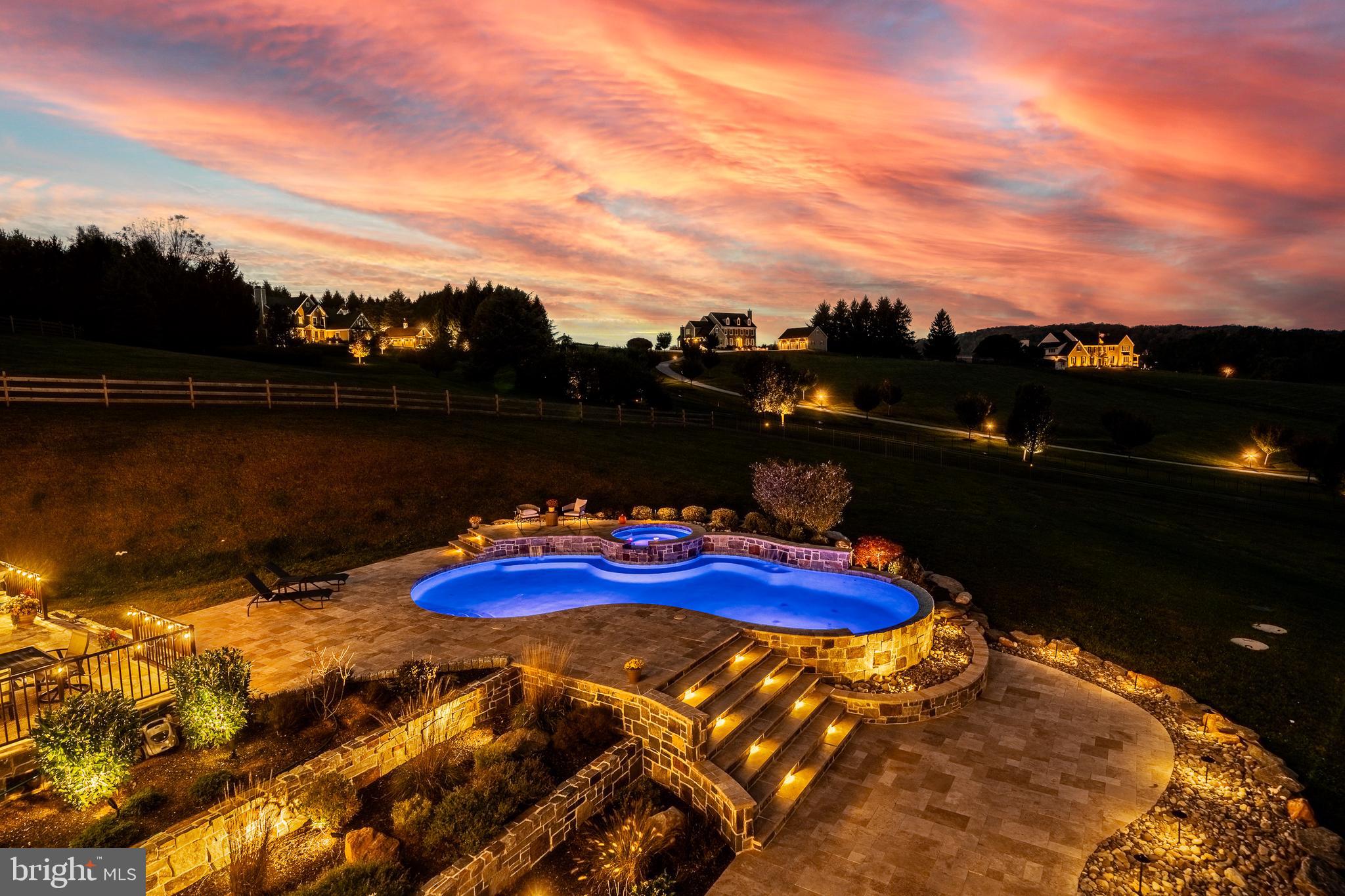 Welcome to 45 Wyndemere Lake Drive, a two years young luxury estate perfectly perched on 6.4 acres in the heart of Chester County, offering unrivaled 180-degree panoramic views of the rolling Chester Springs landscape. Arise viewing the sunrise in the morning and allow the setting sun to wind down your day peacefully as you view it from your kitchen, great room or poolside. This one-of-a-kind residence was meticulously designed to blend modern architecture with biophilic design principles, bringing the serenity of nature indoors through light, texture, and organic materials. Step inside and experience an atmosphere where every detail is intentional and every view feels like a painting. The home’s Rocky Mountain–inspired architecture features floor-to-ceiling Anderson windows for the panoramic Chester County views, hand-selected quarry stone, and beautiful wood beams that flow seamlessly throughout. The open-concept great room and chef’s kitchen form the heart of the home—showcasing leathered granite countertops, an expansive entertaining island with a lowered baking counter, top-of-the-line Sub-Zero, Wolf, and Cove appliances, and a butler’s pantry with custom cabinetry. A cozy breakfast nook framed by a uniquely designed wood-planked ceiling and built-in seating captures the morning light, while the dining room impresses with grass cloth wallpaper, stained-glass pocket doors inspired by Frank Lloyd Wright, and serene views of the outdoors.  This thoughtfully designed floor plan offers two luxurious primary suites, each with private balconies overlooking the pool and sweeping vistas. One suite includes a private office, while another has a connected accessible bath and walk-in showers showcasing universal design at its finest. A first-floor study with custom built-ins and a dedicated yoga room with breathtaking window walls create perfect environments for work or reflection. Every aspect of this home was crafted to engage the senses: from the grass cloth wall coverings and natural wood cabinetry, to the custom hardwood floors and bespoke lighting in chrome, steel, brass, and teak. Even the dog wash room, located off the mudroom and garage, was designed with ergonomic practicality and care in mind.  Step outside and discover a backyard oasis that rivals a luxury resort—featuring a freeform infinity-style pool with a built-in hot tub, waterfall, with app- controlled lighting and temperature, and a three-tiered patio finished with Turkish tile. Gather around the stone fire pit, stroll through landscaped gardens filled with indigenous plants, and take in the showcase lighting that accentuates the boulders and walkways as day turns to dusk. Additional highlights include a three-car garage with an attached shed, geothermal heating and cooling, five thermostats, a whole-house generator, security system, custom window treatments, and a user-friendly gated entry with an app-controlled electronic gate. The “Vega ManaBloc” water distribution system supplies eco-friendly instant hot water to each fixture in the home. Let your imagination run wild with the walk-out lower level offering endless potential —prewired for a media or sound room, and perfectly suited for a golf simulator, pickleball court, or home theater. This extraordinary home is more than a residence—it’s a sensory experience designed to connect you with nature, elevate everyday living, and redefine luxury.