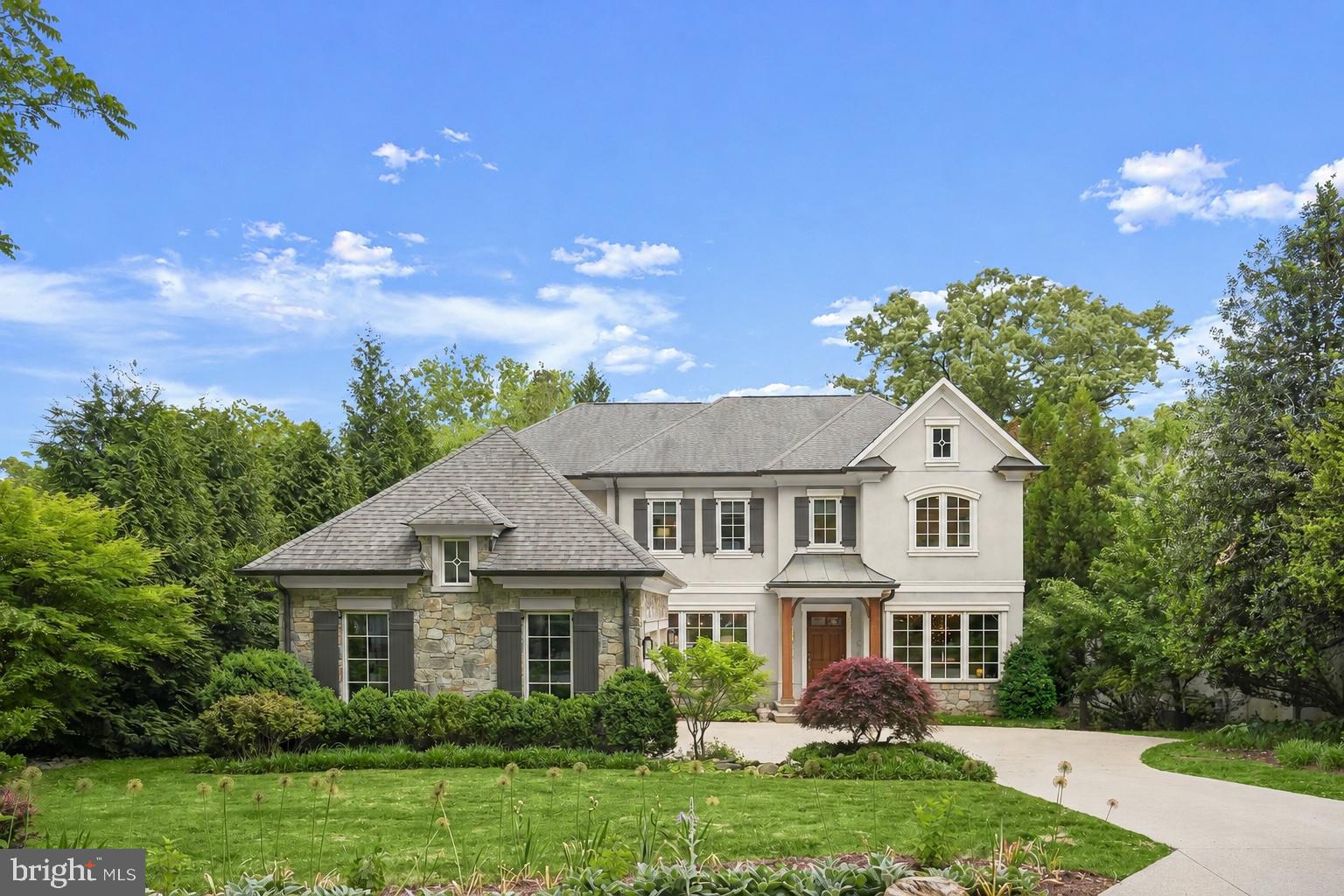 Welcome to 8204 Caraway Street, a stunning stone and stucco residence tucked away on a quiet street just moments from the Potomac River. Set on a gorgeous flat, pool-sized lot surrounded by mature trees and lush landscaping, this exceptional five-bedroom, four-and-a-half-bath home combines timeless architecture with modern luxury living. Thoughtfully designed with beautifully curated finishes, the home offers an ideal balance of elegance, warmth, and functionality.

A gracious foyer opens to expansive, light-filled living spaces with soaring and coffered ceilings and peaceful views of the backyard beyond. Designed for both elevated entertaining and everyday comfort, the main level features a formal dining room with a stylish wet bar and discreet access to the kitchen, a sophisticated formal living room, and a private library ideal for today’s work-from-home lifestyle. The spacious family room is anchored by a striking stone-surround gas fireplace and opens seamlessly to the covered porch and backyard, creating effortless indoor-outdoor living.

At the center of the home, the oversized gourmet kitchen is both functional and beautifully appointed, featuring a Sub-Zero refrigerator, 48” Wolf gas rangetop, double ovens, an expansive 10-foot island with seating, a walk-in pantry, and a sunlit breakfast area. A mudroom with custom built-ins and a powder room connect conveniently to the side-entry two-car garage. The covered porch and expansive rear deck overlook the tranquil, tree-lined yard, offering exceptional privacy and plenty of space for a future pool.

Framed by oversized windows, the staircase leads to a spacious upper-level lounge, ideal as a secondary family room, office, or study space. The luxurious primary suite offers coffered ceilings, abundant natural light, and a private balcony overlooking the serene grounds. A boutique-style walk-in closet with custom built-ins and a center island pairs beautifully with the spa-inspired bath, complete with dual vanities, soaking tub, oversized walk-in shower, and designer finishes throughout. Three additional spacious bedrooms with hardwood floors, generous closets, and en suite bathroom access complete the upper level.

The fully finished daylight walkout lower level is designed for entertaining and flexible living, featuring an expansive recreation room with direct access to the patio and backyard. A fifth bedroom with an adjacent full bath offers the perfect setup for guests, an au pair, or extended stays. Ideally located near the C&O Canal, shops, restaurants, downtown Bethesda, and major commuter routes into DC and Virginia, this exceptional home is also part of the highly sought-after Whitman school cluster. Offering charm, character, privacy, and modern luxury in one of Bethesda’s most coveted locations, 8204 Caraway Street is truly a rare offering.