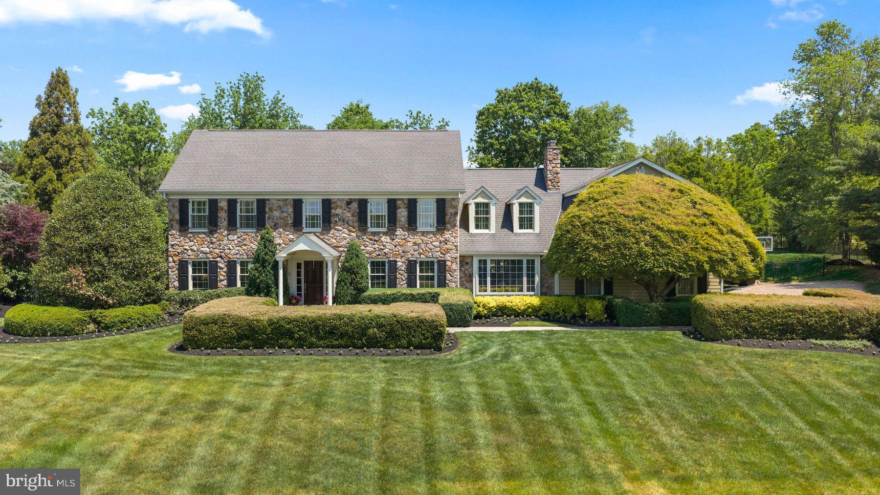 Perched on a beautifully landscaped 1.06-acre lot with a gracious setback from the street, 1017 Lorien Drive enjoys a commanding presence on one of Gwynedd Valley's most iconic addresses and offers more than 5,900 square feet of refined living. A dramatic foyer opens to a classic center hall colonial, framed by two divided light french doors leading to the study on the right and a light filled living room on the left.
A distinguished first-floor study showcases extensive custom cherry built-ins and rich wainscoting, and functional cork wall covering. The adjoining living room is bathed in light through floor-to-ceiling windows. At the heart of the home, a stunning kitchen remodeled by Blue Bell Kitchens features a Thermador six-burner range with griddle, two built-in Sub-Zero refrigerators, a Wolf oven, granite surfaces throughout, an oversized island with prep sink, walk-in pantry, built-in desk, and a separate wet bar with custom cabinetry. Three skylights flood the space with natural light, and French doors open to a hardscaped patio and pool beyond. Just off the kitchen, the family room invites everyone to linger with floor-to-ceiling built-ins, a coffered ceiling, and a cozy window seat, while a sunroom wrapped in windows captures the gardens year-round. To complete the first floor, a stunning dining room with room to host everyone for the special meals, like Thanksgiving, or just your average Sunday night!
Upstairs, the center hall corridor services six generously scaled bedrooms, a full laundry, and second floor office and sitting area. The primary suite is a true retreat, featuring a private sitting room, three walk-in closets, a skylit vanity area, and a spa-inspired bath with cathedral ceilings, additional skylights, his-and-her vanities, and radiant-heat floor. Three additional bedrooms with adjoining baths, a second home office, and a laundry room complete the level. A private two-bedroom suite over the garage offers ideal accommodation for in-laws or an au pair. The lower level extends the living space with a finished entertainment room featuring a built-in bar, plus extensive built-in storage and work bench in the unfinished area.
Step outside to your own private resort: a sparkling pool framed by a bluestone patio and cool-deck surround, lush professional landscaping, and two graceful fieldstone retaining walls. A full pool house with kitchenette, full bath, changing area and potting shed/storage completes the picture. A whole-property sprinkler system fed by a private well keeps the grounds effortlessly verdant. Award-winning schools, convenient shopping in Spring House and along Route 309, an easy commute to Philadelphia via the regional rails, and a short drive to the Trenton train station to catch Amtrak to NYC round out a rare opportunity to plant roots on one of Gwynedd Valley's most coveted streets.