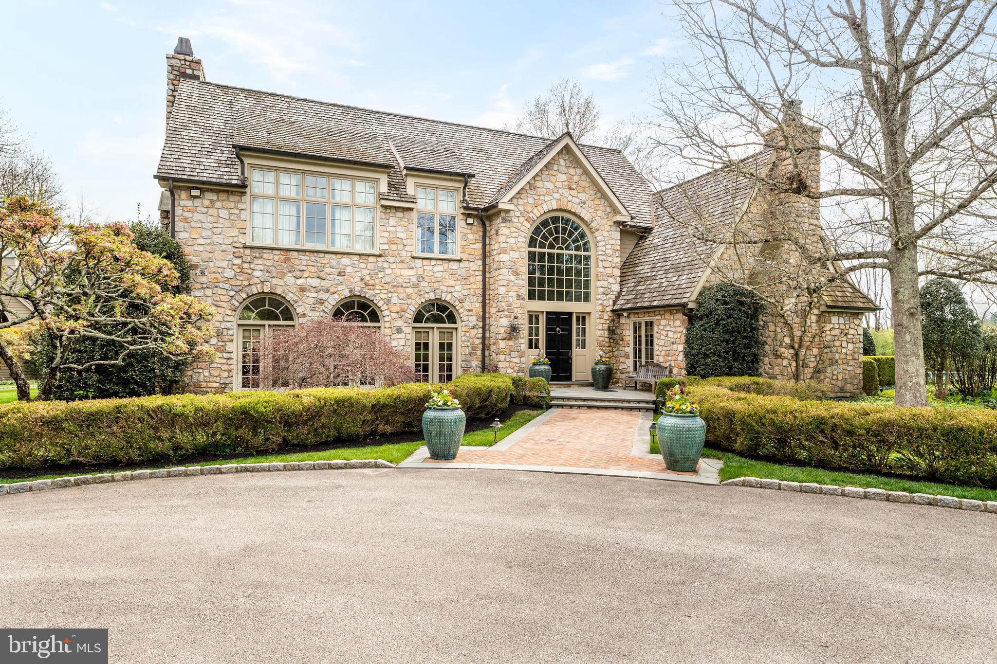 Tucked away on a private drive built on 2.8 serene acres in prestigious Gwynedd Valley, this beautifully landscaped custom built estate home is a stunning blend of timeless elegance and modern luxury. Driving up the private drive to this home will truly take your breath away.
This one of a kind home offers a thoughtfully planned layout of over 11,000 square feet, with amazing views from nearly every window. Hardwood flooring, exquisite mill work, arched doorways and beautiful Pella french doors and windows are just a few of the quality details to be found. It combines formal and casual living to accommodate all lifestyles and the attention to detail in this home is undeniable.

As you enter the two story, light filled foyer you are immediately impressed by all the details. Flanked on one side of this grand entrance there is a gorgeous two story wood paneled library with wet bar and stone wood burning fireplace and the other side opens up to the formal living and dining room with the perfect ambiance to entertain family and friends.
The chef’s dream kitchen features a large center island, multiple work spaces, luxury appliances, and walk-in pantry. A cozy family room off of the kitchen features a gas fireplace and intricate custom molding. For the wine enthusiast, a back bar room offers chilled wine closet, wet bar with a custom wooden sink, and wood-burning fireplace. All rooms lead to gorgeous blue stone covered patio spaces that include a built -in barbeque, large stone outdoor fireplace and TV.

On the second floor the owner’s suite offers a spa-inspired bathroom, custom closets, and breathtaking views. Also find three generously sized bedrooms all with en suite bathrooms and walk in closets. On third floor find two additional bedrooms adjoined by a jack and jill bathroom.

The finished lower level completes this home with a theater room, gym, half bathroom, and spacious play room for adults and children alike. Don’t miss out on the opportunity to create a golf simulator space and expansive wine cellar.

Walk out to the rear yard to find beautifully manicured lawn and a new custom in ground pool built in 2025. A carriage home with two car garage has a finished upper level with full bathroom. The three bay garage has unfinished storage above that can be converted into a great art studio, office or additional living space.

With radiant heated floors in select rooms, a full-house generator, an irrigation system, full house water softener, and water detection system and sophisticated security system, this property is as practical as it is beautiful. Positioned for both privacy and convenience, it is located nearby several train stations, all major highways and Ambler’s vibrant dining scene.

Listing Agent is related to seller.
