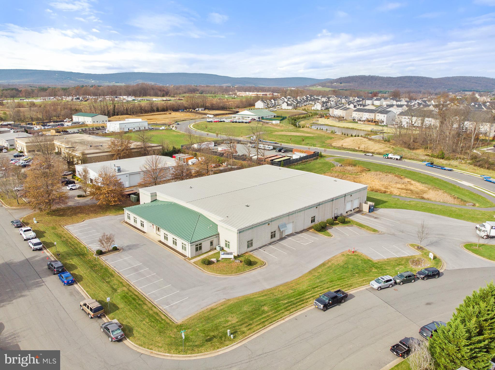 27,000 SF free-standing, Class A industrial building in Purcellville, VA. Built in 1998, the property was purchased by the current owners in 2006 and has undergone numerous renovations as recently as 2018. Home to Shenandoah Sash & Door for nearly 15 years, every square foot of the property reflects the luxury and style that its customers have come to know; from high-end built-in cabinetry and bookcases to decorative moulding and wainscoting throughout. The value of the windows and doors, alone, is in the tens of thousands. If this were not enough, the property comes fully furnished and beautifully decorated. In addition to the typical desks and chairs, leather furniture, hardwood conference tables, attractive art, faux plants, mounted televisions, and file cabinets may convey with the sale; elevating this beyond a mere plug n’ play deal to an inheritance of meticulous attention to detail, quality, and class.   Approximately 200’ long by 140’ wide, the building sits on 1.86 acres with over a half-acre parking lot which provides 18-wheelers with easy access to the property’s 2 loading docks and drive-in door along with ample parking for cars and trucks. The warehouse has 25’ x 50’ column spacing and 16’-18’ clear height with upgraded lighting and ductwork in place to condition the entire space. The 21,000+ square feet include approximately 1,800 SF of showroom space, a 400 SF workshop, a small office and bathroom, and grand conference room. A perfect mix of utility and elegance.  For employees and customers, the first impression of the property is a mix of simplicity and beauty; perfect proportions, clean lines, and manicured landscaping. Meticulous and intentional. The 3,300 SF of office space opens to a sunlit foyer with mosaic tile. One’s view is immediately drawn to the right due to the architecturally stunning, curved glass wall of the conference room, perhaps more accurately titled the closing room, which is directly across the hall from one of the 6 large, windowed offices. While one of the 2 corner offices is for the company's executive, the other 5 are multi-person offices and the other 4 interior offices are bright with a mix of glass doors and cased openings. The elegant but economical kitchen features stylish countertops, designer fixtures, and ceramic tile; the quality and consistency of which extend to 2 ADA bathrooms. Whether a weekday or weekend, a sunny day or cloudy, this is a welcoming and energizing environment.  Quality and quantity are seemingly conflicting concepts, or rather ones with a proportional relationship similar to supply and demand, and rarely do both present themselves in perfect harmony as they do here. The 2019 SIOR Industrial Report predicted a 10% increase in capital investment and continued cap rate compression in 2020 prior to the pandemic. Industrial space has been the only real estate asset class to perform well and actually increase in value during this time; a natural progression but one accelerated by the increased need for storage and distribution. This is not just storage of products. It refers to data as well. The fact that Loudoun County is home to 70% of the world’s internet traffic has contributed to industrially-zoned land selling for $1M/acre. Thirty minutes from Dulles Airport and less than 10 miles to Leesburg, this property presents a rare opportunity to own a free-standing industrial building under 50,000 SF and provides a competitive advantage to storers and distributors of either data or products as the western-most industrial development in Loudoun County, making it the last, last-mile delivery station. It is the 3rd largest building and comprises over 10% of the Purcellville industrial market.  With a market sales price of $216/SF for the Purcellville industrial market, the asking price of $203.70/SF represents over $330,000 in savings/value, a cost of ownership that is over $1.00/SF lower than