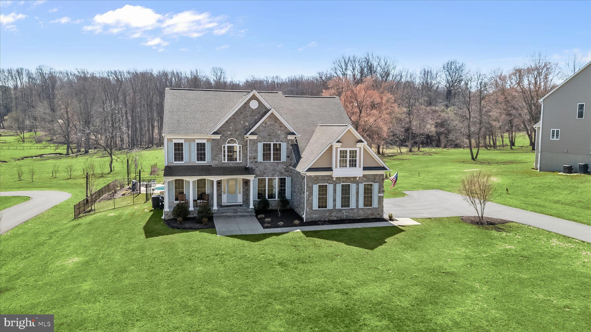 Welcome to this beautifully appointed home nestled on a picturesque, private, expansive lot, showcasing refined luxury master craftsmanship, & exceptional outdoor living. From the moment you arrive, you’ll be impressed by the home’s stately curb appeal, charming stone façade, & inviting flagstone & stone front entryway & covered porch.
Step inside to a bright, open interior featuring soaring ceilings, abundant natural light, & elegant finishes throughout. Transitioning from the two story entrance foyer, the formal living room resides to the left, offering hardwood flooring, generous crown molding & an architectural column. To the right of the entrance foyer is the grand dining rm, wrapped in chair & crown moldings, a tray recessed ceiling, hardwood flooring, w/oversized windows offering sun drenched natural light, perfect for accommodating large family holiday meals/entertaining. The dramatic two-story family room, anchored by a gas fireplace and framed by an upper-level overlook, creates a grand, yet inviting atmosphere ideal for both everyday living & upscale entertaining. The beautifully updated gourmet Chef's kitchen is equipped with a GE double oven, GE 5-burner gas cooktop, GE range-hood, large quartz island, with tuck away microwave storage cabinet, Whirlpool refrigerator and dishwasher, pantry, coffee bar, glass subway tile backsplashes, and breakfast seating with beautiful tray recessed ceiling, peering out into the expansive country club backyard setting. A fifth bedroom with attached en suite full bath & double closets is tucked back on the far left, behind the family rm. It is currently staged as on office for convenient hybrid work schedules. The powder room bath  with quartz countertop and ceramic tile flooring completes the main level. 
The home features five bedrooms and five full baths, and one half bath. Two ascending hardwood staircases usher you to the second story landing. The catwalk transports you to the right to french doors securing the primary luxurious owners suite, boasting tray recessed ceiling and ceiling fan, an attached sitting room, custom wood blinds and 2 walk in closets with built ins. Another set of French doors guides you to the spa like bath, featuring soaking  tub, double sinks, quartz counters, custom wood blinds colossal size stall shower, private commode area and thoughtful floor heater. Opposite the primary bedroom suite is a large guest bedroom with attached en suite full bath. Across the other side of the catwalk, are two additional spacious bedrooms adjoined by a Jack and Jill full bath which rounds out the upper level. 
The descending hardwood staircase  to the lower level leads to an additional full bath, large recreational room for games and family fun, and utility and storage rooms with ample space waiting for your creative finishing touches. Lower level can easily add another enclosed 6th bedroom making it ideal for a multi-generational living arrangement, au-pair or in law suite as it has its own private walk up staircase to the rear paver pool area.
Outdoors, your private backyard oasis awaits. Enjoy a beautifully designed in-ground propane heated saltwater pool w/attached spa installed in 2022, surrounded by a generous paver patio & lush landscaping, trex deck, ideal for relaxing or hosting gatherings. The property backs to sweeping green vistas w/pastural & scenic views, creating a peaceful, retreat-like setting. 
Additional highlights include a spacious paved driveway, well-maintained manicured grounds, a layout designed for comfort & functionality, 380 leased solar panels for an environmentally friendly power source which have been providing about 80% of the homes energy needs ( sellers will pay off the solar lease at or before closing) & a 3-car side loading garage w/built in 32 amp EV charging line.
A rare opportunity to own a home that perfectly blends elegance, space, & lifestyle just minutes from everyday conveniences while offering a serene, countryside feel.
