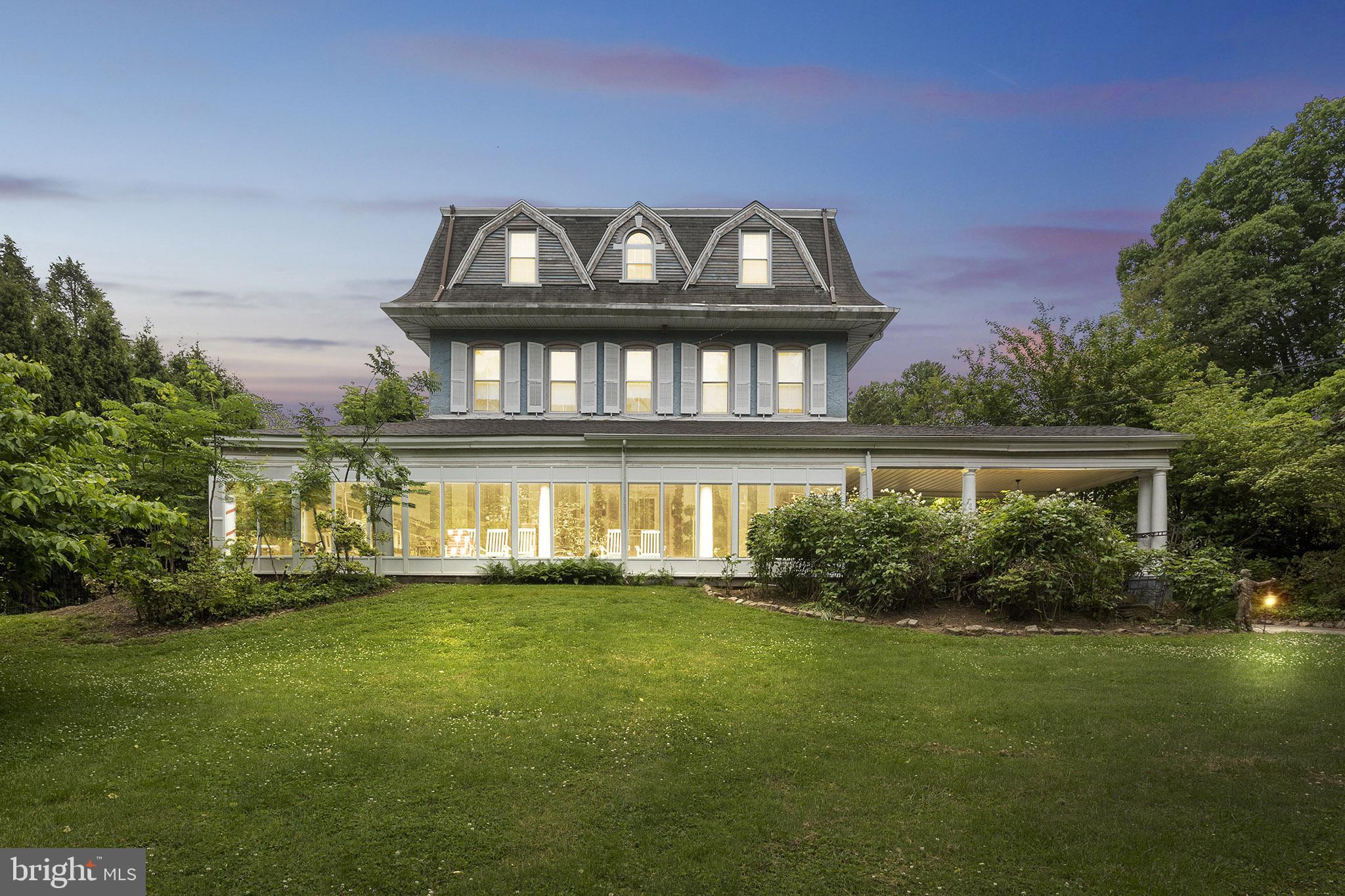 Incredible opportunity to purchase a piece of Main Line History! The house, constructed of stone, is of Victorian style, with typical architectural elements such as a Mansard roof with dormers, a large wrap around porch and projecting bay windows. A gabled porte cochere welcomed horse drawn carriages when built, and now serves as a circular driveway for modern use. Exquisite features include 10 ft ceilings on the main and second levels, original leaded glass details on some windows, grand entertaining spaces and a dramatic wrap-around front porch overlooking the private grounds. This five bedroom, four full and three half bath home has been well maintained and expanded through the years for modern living. This property is registered as a Class II Historic property with Lower Merion Township. An extensive renovation and expansion was completed in 2003. Recent upgrades include new roof (2023), new multi zone HVAC systems (2025), new hot water heater (2025). Beautiful original chestnut wide plank floors greet you in the center hall foyer and run throughout most of the main level. To your right sits the study complete with floor to ceiling windows, custom-built mahogany shelving and matching crown and baseboard moldings. The formal dining room sits opposite the study with white painted moldings, floor to ceiling windows with built-in benches & a cozy wood-burning fireplace at the center. A butler’s pantry connects the dining room to the living room, providing an extra serving area for entertaining. The spacious living room features beautiful leaded glass paneled windows, built-in window seating & a wood-burning fireplace tucked away under a graceful archway in the center of the room. The gourmet kitchen was renovated and expanded in approx. 2003 and is the showpiece of the home. A nineteen foot long island runs the length of the kitchen and provides an abundance of storage along with hosting both counter height & bar height seating. The painted wooden cabinetry is complemented by black and white tile flooring, light granite countertops, two large stainless steel refrigerators, a gas range, double wall ovens, and dishwasher. The tile flooring flows into the oval shaped great room at the end of the kitchen which is flooded with natural light from the french doors and Palladian-style windows. A large laundry room is located off of the kitchen with washer, dryer, sink and folding area. Additionally, there is a half bath located within the laundry area. The second floor hosts the primary suite with high ceilings and a wood-burning fireplace. The Palm Springs spa-inspired ensuite boasts dual vanities, a large jetted soaking tub, and a glass-enclosed stall shower, all highlighted by beautiful tiling and detailed moldings. There is a large home office boasting an oversized bay window situated behind the primary bedroom. Just beyond the office area is a second level addition currently used as an entertaining space with three elevations of windows, vaulted ceilings, skylights, and a custom-built full wet bar. A secondary ensuite bedroom rounds out the second floor, and boasts high ceilings, ample closet space, and an abundance of natural light. The third level hosts three additional spacious bedrooms, as well as two full bathrooms and a hall closet. There are numerous outdoor entertaining areas including a large stone terrace overlooking the private backyard area. There's an in-ground pool with surrounding brick patio (in need of restoration), surrounded by mature trees and the ultimate in luxurious privacy on the Main Line. Since the property is a Class II Historic site, the zoning allows for limited commercial use. For any commercial use within this residential historic zoning, the home must be owner-occupied. While the home has been maintained throughout the years, the current price reflects the opportunity for a buyer to continue to restore this magnificent Main Line estate.