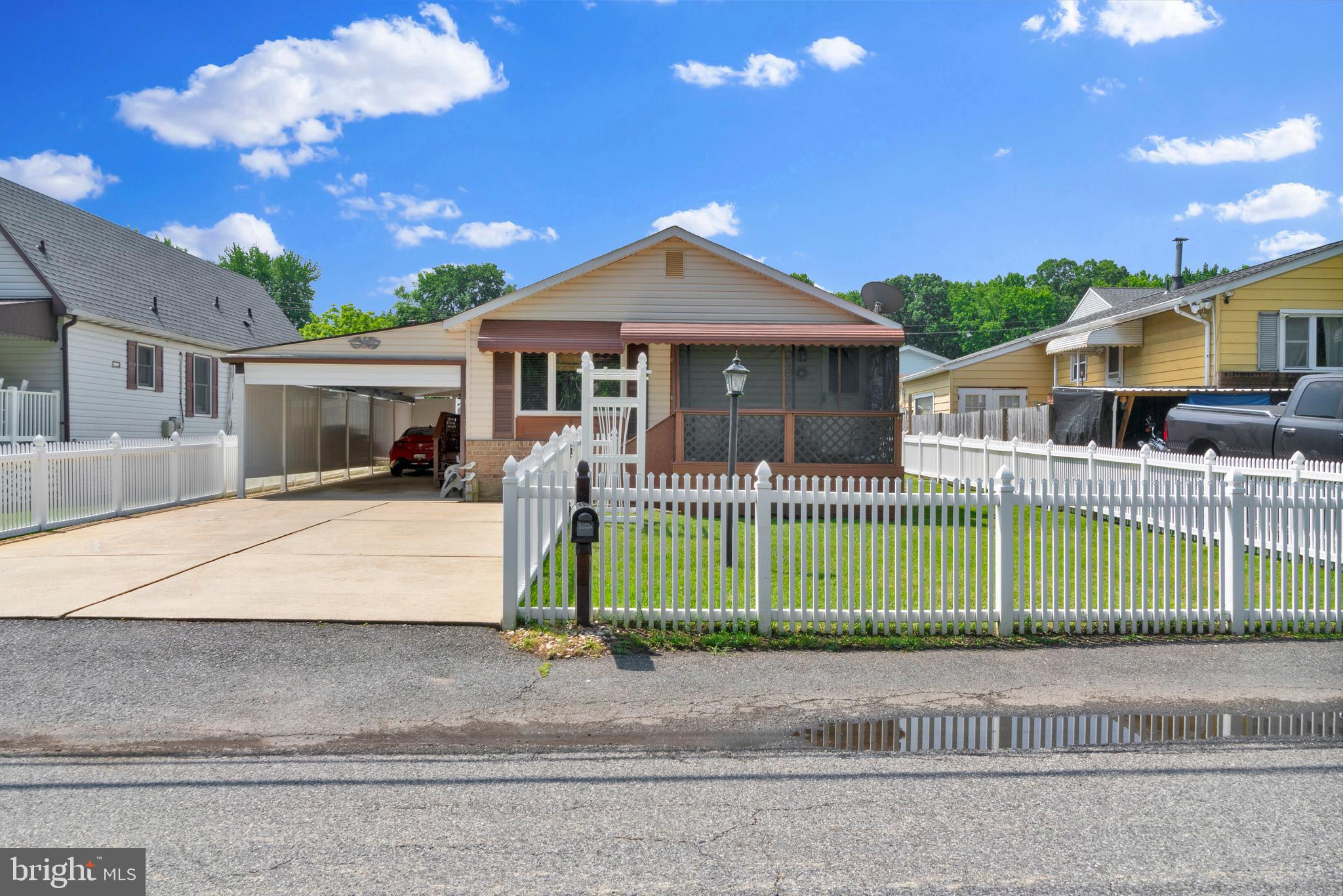 Welcome to 8029-A Shore Rd & enjoy one level living in desirable Sparrows Point! This 3 Bedroom 1.5 Bath home is ready to welcome you to the community with a vinyl white picket fence surrounding the grounds. Enter the living room to a traditional but spacious floor plan. There is a bow window illuminating the space with natural light. The kitchen has plentiful counter space for food prep & wood cabinetry. Above the double sink is the greenhouse window, perfect for plant lovers & fresh herbs. There is space for a large kitchen table as well. Down the hall is the full bathroom with a tub shower combination & updated flooring. All three bedrooms are carpeting with the primary offering an attached 1/2 bath. Pull down attic stairs give access to additional storage space above. Relax on the screened front porch away from bugs and from stress. There is a large carport over the concrete driveway with lighting. When not used for parking, this could be a great space for outdoor entertaining in the shade. The rear yard offers 2 sheds, one with loft storage space & electricity. Have peace of mind with the remainder of the First American Home Warranty through March 2027.