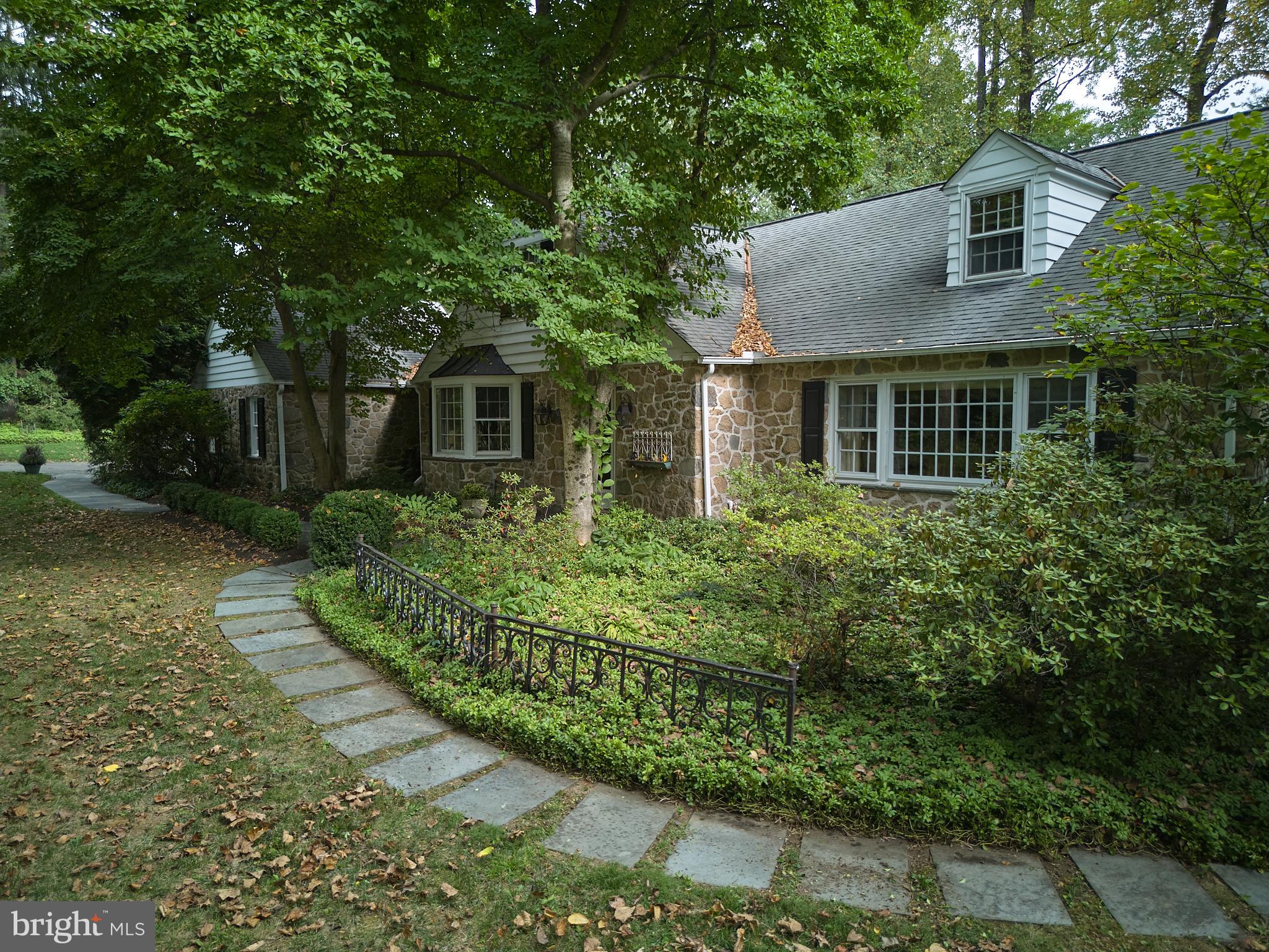 Welcome to 741 North Ithan Avenue in Bryn Mawr, PA!  This very charming, roomy, stone cape is sited on a picturesque 1.06-acre lot. The inviting home boasts 4,232 square feet of very comfortable, livable space including all levels.
As you enter the gracious front hall, you are greeted by a bright, spacious living room with a wood-burning fireplace and a large picture window.  You pass through to the dining room- both rooms are ideal for gatherings and entertaining- into the sun-filled garden room with its cathedral ceiling and three walls of windows offering a serene retreat with egress to a very private, oversized Pennsylvania flagstone terrace complete with a sitting wall.
Back inside, the all-white kitchen is a chef's delight, featuring high-end appliances and a large island perfect for less formal, seated meals.  Adjacent to the kitchen is an inviting library/office with bay window and built-ins and direct access to the breezeway and garage.
The main floor presents a flexible living arrangement with a primary ensuite wing that can be closed off from the other rooms on the first floor.  This wing features a den (additional bedroom?) and a full bathroom.  The second-floor houses three generously sized bedrooms and another full bathroom, ensuring ample space for children or guests.
The finished basement adds even more living space, with a laundry area, a cozy playroom with a fireplace, and a tiled storage area.
This charming home combines classic design with modern, open, bright spaces, making it a unique find in a great walking neighborhood.  Don't miss the opportunity to make this beautiful property your new home.