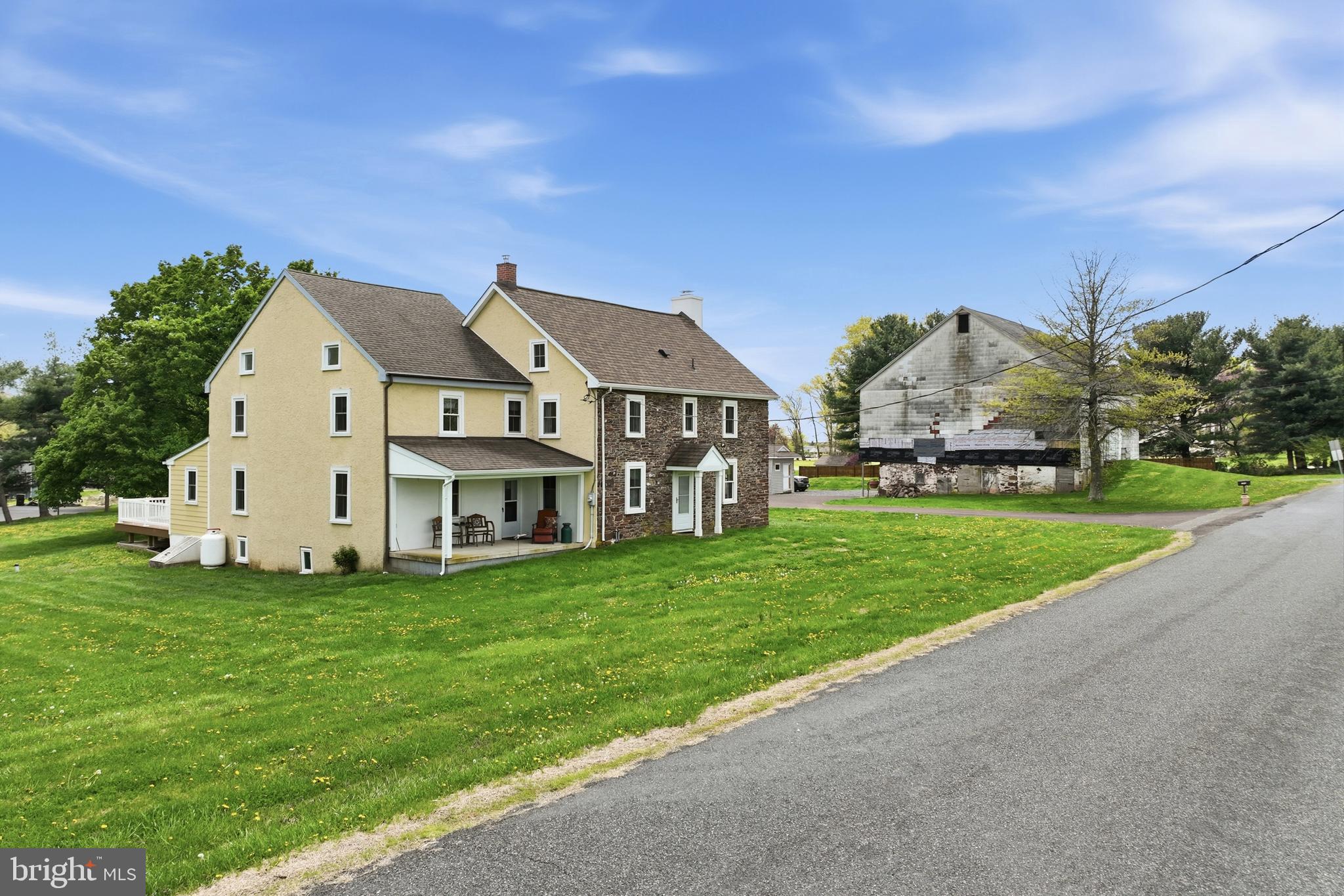 This circa 1756 stone farmhouse is rooted in tradition and is a salt of the earth authentic colonial era home that radiates quiet dignity and rustic simplicity. It's a historic home that has grown over time, blending original 1750s craftsmanship with later additions.
It was crafted from local indigenous materials, “such as roughhewn logs, native fieldstone and original wide plank floors. It's a timeless piece of colonial history that has weathered and evolved over 250 years.
It's situated on a 2.45-acre lot that is adjacent to a 48-acre farm field that yields corn or soybean crops annually. 
You will enter the home through a bright cheery sunroom. It’s a perfect place for your plants and the dogs or cats to lounge in the brilliant sunlight. It boasts of wide plank hardwood floors and skylight. Next is the spacious foyer with a convenient slate floor and convenient closets and shoe racks. 
Imagine yourself snuggling up in the warm and inviting family room on a cold winter night. This haven features exposed stone walls surrounding a wood burning fireplace. There are built in cabinets and bookshelves, wainscoting, wide plank hardwood floors and exposed hand-hewn beams. It will be the gathering place after a family dinner. 
The large country kitchen has been remodeled and features classic beaded inset cabinets, propane stove, microwave, granite counter tops, hardwood floors, deep country sink and stainless-steel appliances.  The adjoining breakfast nook is spacious and provides an ideal place for your informal meals or your morning cup of Joe.  Overhanging the granite counter tops is a timeless potholder for all of your pots and pans. 
Directly beyond the eat in kitchen is a formal dining room with exposed stone walls and sparkling hardwood floors. 
The remainder of the first floor has many possibilities according to your needs. There is a central room that currently serves as an office but could be a possible in-law suite or Au Pair suite. It has an adjoining second kitchen and a powder room. Directly off the second kitchen is a new composite deck for a possible barbeque or evening beverage retreat.
A newer addition to the home is a renovated space that currently serves as an office for the current owner.  It has many potential uses, and you can use it for your best purpose. The two rooms have high ceilings with very appealing architecture.  There is a new high efficiency heat pump for your cooling and heating. Some possible uses are a second family room, home office, in-law suite, game room, etc. Use your imagination. 
Retire to the second floor to find a large master bedroom area. It features hardwood floors, open beam ceilings and a remodeled bath. The bath includes a walk-in shower, soaking tub for your aching bones and his and her walk-in closets. The remainder of the second floor consists of four additional bedrooms, all of ample size and a remodeled hall bath with ceramic tile floors and glass shower. The third floor of the home features a fifth bedroom that is tucked away quietly. It would make a perfect teenage haven or guest room.
The entire home is warm and inviting. It's a perfect blend of old and new and has stood the test of time.
The possibilities are endless for the use of the three out-buildings. They include a three-car garage that measures 40x25 feet. It's a perfect place for a serious hobbyist or car collector. It has second floor storage as well as ample floor space. Additionally, there is a pole barn that currently serves as a storage area for the current owner’s business supplies. It's complete with a heated powder room and the possible uses are endless. 
The huge two-story bank barn measures 46x52 and needs some exterior siding repair but is generally in very solid condition. It has enormous possibilities and awaits your finishing touches. 
There are two smaller sheds as well for tool storage. At the rear of the lot is an old, paved tennis court. It's currently serving as a parking area for trailers.