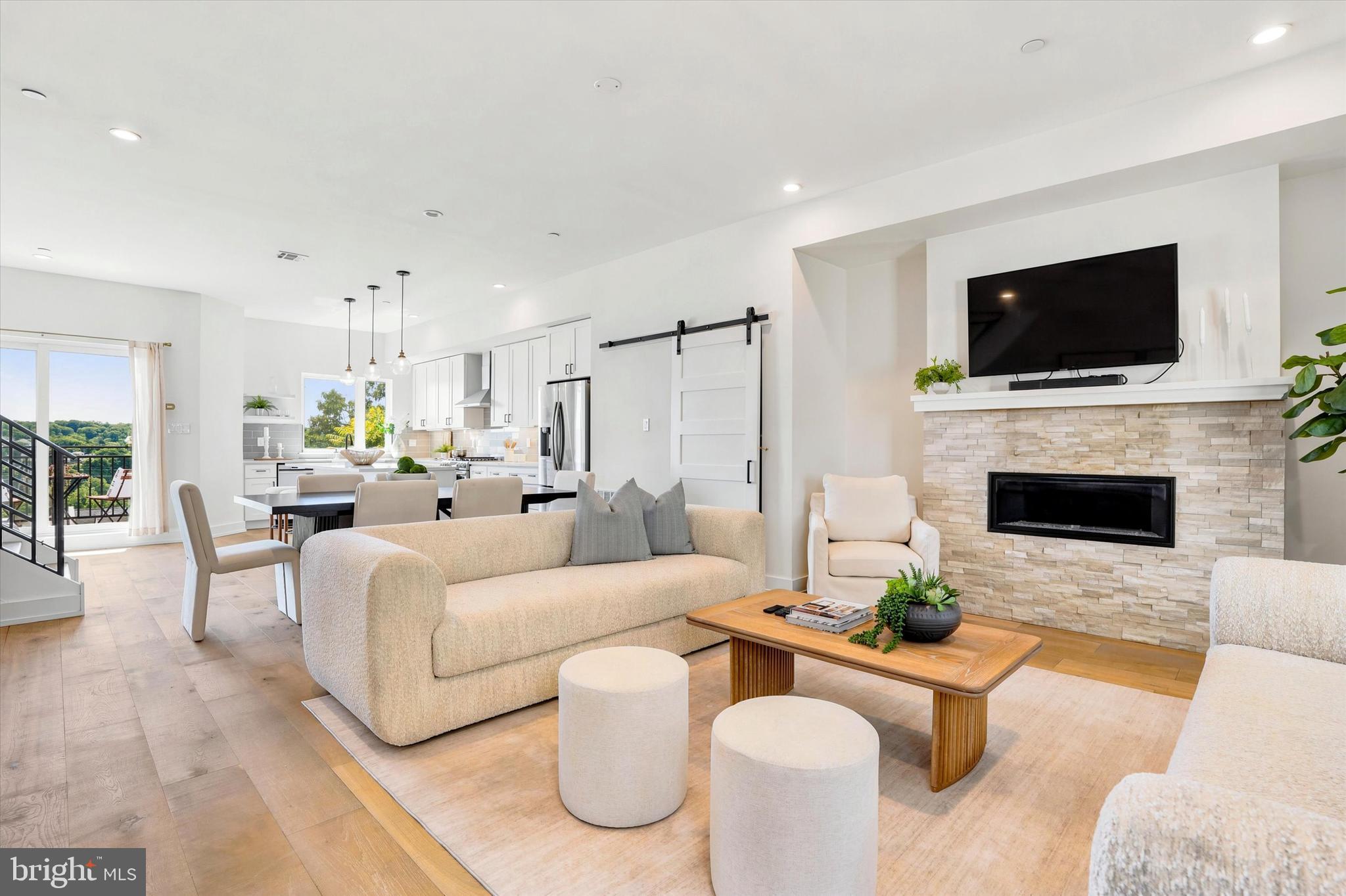 Elevated luxury meets panoramic views in this perfectly pristine, "former model" townhome perched high above the Schuylkill River Valley close to downtown Manayunk. Presenting an exceptional 3 BED, 3 FULL BATH residence with 2 CAR ATTACHED GARAGE offering an unparalleled blend of indoor and outdoor spaces and scenic tranquility. Built in 2021 as the model home for Hermitage Place—an exclusive collection of eight luxury townhomes—Unit #7 features thousands of dollars in PREMIUM BUILDER UPGRADES and with 5 YEARS REMAINING ON THE TAX ABATEMENT, this home offers its new owner substantial financial savings alongside a blend of high-end design and everyday comfort. Tucked away off the street and perched high on the ridge, the property commands panoramic views of Manayunk and beyond, as it integrates indoor and outdoor living across three distinct exterior spaces: Enjoy summer grilling on the main-floor kitchen patio, or retreat to the expansive rooftop deck with an expanded wet bar just steps below; the roof deck can serve as both a peaceful morning yoga sanctuary and a dramatic setting for evening entertaining against a backdrop of beautiful sunsets. The remarkably flexible floor plan spans multiple finished levels. The entry level welcomes you with a spacious foyer, a stylish full bath, and a good sized bedroom—perfectly suited for a private guest suite, in-law quarters, or a large home office. Below, is spacious lower-level family room (or 4th bedroom?) featuring high ceilings, recessed lighting, and abundant storage. The main living floor is a dramatic, sun-drenched showpiece. Soaring ceilings, wide-plank wood flooring, comfy window seat /storage and oversized windows create a bright, airy ambiance, centered around a chic gas fireplace with a stacked stone mantle. Unlike typical narrow city townhomes, this wide layout effortlessly accommodates large, comfortable furniture. The chef’s kitchen is the true centerpiece, boasting a massive Calacatta quartz island, custom cabinetry, stainless steel appliances, a walk-in pantry with a stylish barn door, and custom accent shelving. Above, the upper level is designed as a private sanctuary. The primary suite features a light-filled bedroom, a customized walk-in closet with premium built-ins, and a spa-like bath with an oversized step-in shower and double vanity. A third generous bedroom, a beautifully appointed hall bath, and a dedicated full-sized laundry room complete this spectacular, turn-key home. With all this peaceful tranquillity, you may feel like you’re in a secluded retreat, but you’re actually close to everything: Schuykill River Trail for hikes and bikes, Gorgas Park for fun seasonal community events, downtown Manayunk’s Main Street for great eateries, bars and shops; and regional rail line for a quick ride to Center City Philadelphia. Don’t miss an incredible opportunity to own this “like brand new” exceptional home with all the bells and whistles!