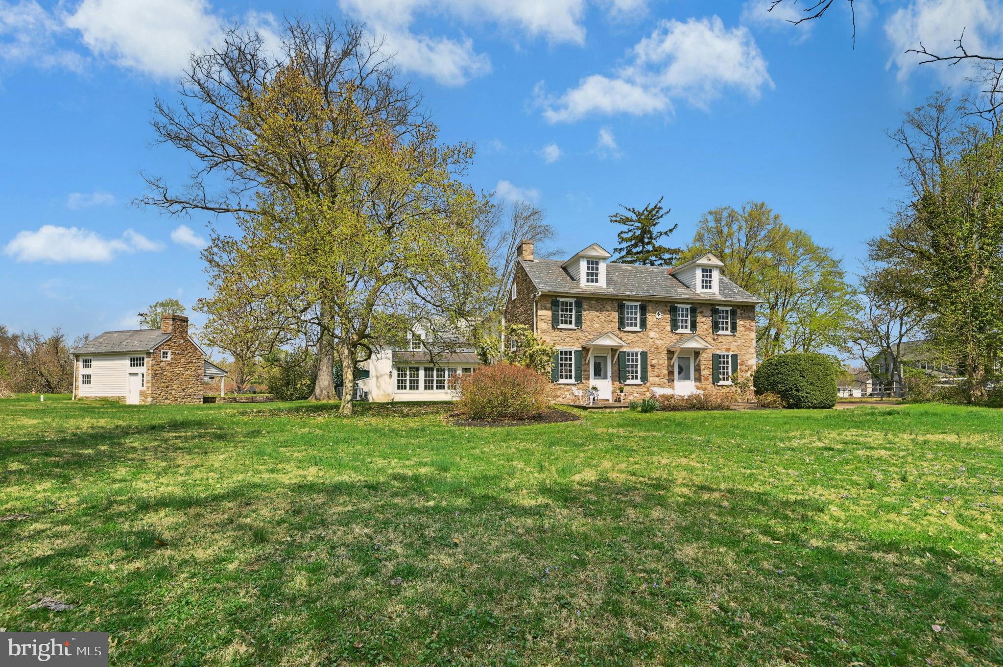 Offered for the first time in more than four decades, this exceptional circa-1752 stone farmhouse presents a rare opportunity to own a historic Bucks County estate combining architectural pedigree, acreage, and modern comfort just minutes from the heart of Doylestown. The home, thoughtfully expanded with architect-designed additions by Ellen Happ and Lynn Taylor, blends period craftsmanship with light-filled living spaces designed for today’s lifestyle. Featuring five bedrooms, three baths, a dedicated home office, and three fireplaces, the residence offers warmth, character, and versatility. A modern kitchen anchors the home, while original details—stone walls, antique wood flooring, and timeless textures—preserve its historic charm. In the cozy morning room, an antique coal stove and oven bring the warmth and character of a bygone era. Generous gathering spaces create a home that is both refined and welcoming. Set on over eight picturesque acres, the property invites a lifestyle deeply connected to the land. Sheep graze across fenced pastures, a chicken coop provides fresh eggs, and mature grapevines and open ground offer opportunities for gardening or small-scale farming. Wooded land to the rear enhances privacy and creates a peaceful natural backdrop—an increasingly rare rural experience so close to Doylestown and nearby Delaware Valley University, with its rich agricultural heritage. Multiple barns and outbuildings support a wide range of uses, all finished with slate roofs accented by metal roofing over porches—reflecting a consistent level of quality throughout the estate. A custom bank barn by Jarrett Vaughan Builders offers flexibility for equipment or livestock. The main barn provides storage for six or more vehicles—ideal for a car enthusiast—with stairs leading to a spacious loft featuring soaring ceilings, perfect for storage, a workshop, or a gathering/game area. This structure is flanked by a carriage house apartment—ideal for a caretaker, guest residence, or multi-generational living—complete with a spacious country kitchen, fieldstone fireplace, and laundry. A greenhouse adjacent to the main barn further enhances the property’s agricultural and lifestyle appeal. Outdoor living is equally compelling. The architect-designed cabana serves as a natural gathering space with a stone, wood-burning fireplace, serving bar, sink, and beverage refrigerator, just steps from the home’s first-floor bath. An in-ground pool, along with patios and porches, creates an inviting setting for entertaining or quiet relaxation. Served by public water and sewer, the property also offers potential for subdivision or future development, subject to township approvals—providing long-term flexibility rarely found in estate properties of this character.
Located moments from the shops, restaurants, and cultural attractions of Doylestown, this remarkable offering combines history, land, architecture, and lifestyle in a way that is increasingly rare in Bucks County.