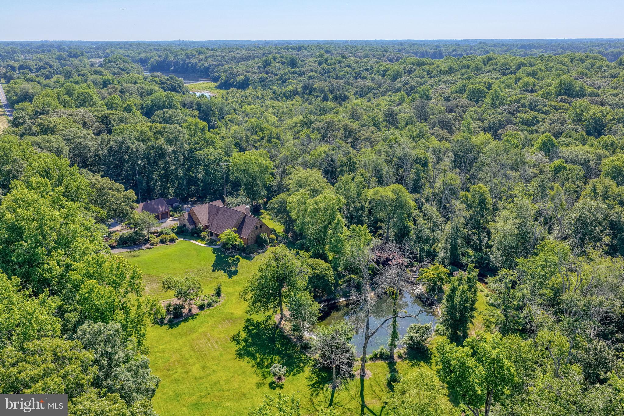A Once-in-a-Lifetime Opportunity on 12.27 Acres! Discover endless possibilities with this extraordinary estate offering two tax parcels totaling 12.27 acres of beautifully maintained grounds. The property includes 7.17 irrigated acres and an additional 5.1-acre parcel, creating a private retreat unlike any other. The award-winning landscape has been recognized as "Garden of the Year" and features meticulously maintained gardens, a picturesque stream and pond, a charming gazebo, and walking trails winding through mature woodlands.The classic Cape Cod home showcases refreshed cedar plank siding, flagstone accents, and brand-new architectural shingles installed in 2026. A newly completed (06/26) 5-bedroom gravity septic system provides added value and peace of mind. Inside, refinished hardwood floors extend throughout much of the first floor, including an elegant foyer featuring decorative parquet flooring. The kitchen blends timeless walnut cabinetry with modern updates and includes stainless steel appliances and two full-size ovens. The sun-filled all-season room, equipped with its own split-unit system, offers panoramic views of Tantrough Branch as it flows from Griffiths Lake to Blairs Pond. Just outside, a spacious deck and hot tub create the perfect setting for entertaining or relaxing. The inviting family room features a traditional wood stove, helping keep utility costs low during colder months. The first-floor primary suite offers hardwood flooring, scenic stream views, a walk-in closet, and a private ensuite bath. Guests will appreciate the additional first-floor two half baths.Upstairs, you'll find four additional bedrooms, a large bonus room, and a  full bath. A cedar closet adjacent to the bathroom presents an excellent opportunity for a second upstairs bath or laundry area. A pull-down attic provides additional storage space, while the whole-house fan allows cool evening air to circulate naturally during summer months. The home is served by a dual HVAC system, including a heat pump and a geothermal system replaced within the last decade. Built with exceptional craftsmanship and durability, the home features 12-inch block construction, a testament to the quality and attention to detail rarely found today. The mostly finished basement offers versatile living space ideal for recreation, fitness, or relaxation, highlighted by a beautiful flagstone gas fireplace. Additional storage rooms, utility sinks, a central vacuum system, and utility areas provide outstanding functionality. A stairway leads directly from the basement to the oversized attached two-car garage. Additional improvements include:
-Detached matching three-car garage with unfinished attic space above
-Heated in-ground pool with diving board and slide
-Stamped concrete surround and black aluminum fencing
-Two Amish-built storage sheds with electricity
-Expansive outdoor entertaining areas
Whether you're seeking a private family estate, exploring the potential for a boutique venue or bed-and-breakfast opportunity, or simply looking for an exceptional property to call home, this remarkable offering delivers.An appraisal on file exceeds the current listing price, presenting a rare opportunity for immediate equity and future customization. Properties of this caliber seldom become available. Schedule your private tour today. The property has been well maintained and is in good condition being sold as-is. Listing Agent is related to Seller, however has no financial interest.