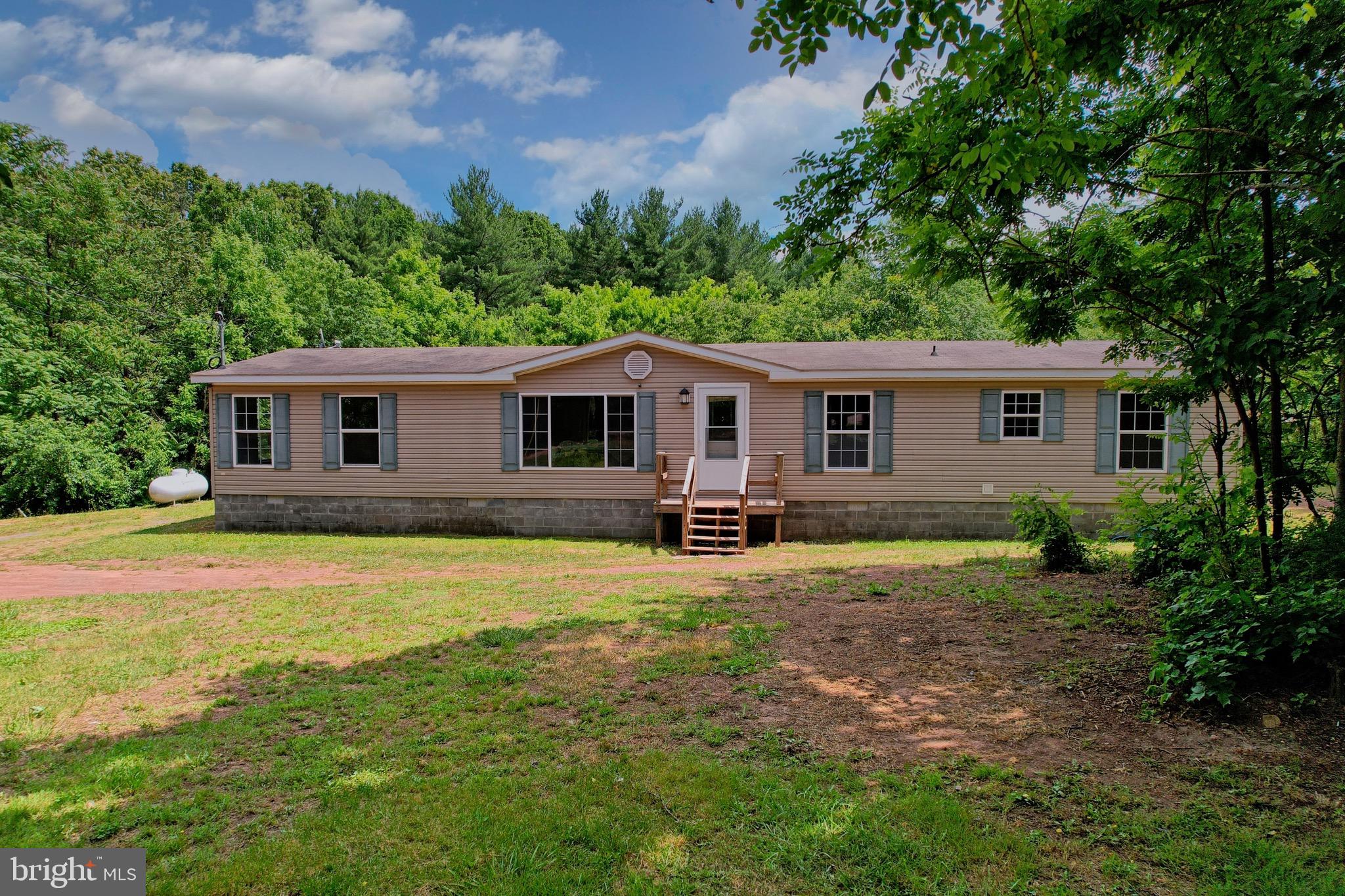 Escape to the peaceful countryside with this beautifully updated 4-bedroom, 2-bathroom manufactured home situated on 5.53 private acres. While the mailing address says Paw Paw, you'll enjoy the convenience of being located right in Slanesville! Step inside to a spacious, freshly painted floor plan featuring numerous recent updates, including luxury vinyl plank flooring throughout, new carpet in the primary bedroom, updated light fixtures, new storm doors, and new sliding glass doors. The kitchen has also been refreshed with a new refrigerator and dishwasher, making it move-in ready from day one! The home offers comfortable living spaces designed for both everyday living and entertaining. Outside, you'll find the perfect space to relax, entertain, or simply take in the surrounding natural beauty. Backing to common land, this property offers added privacy and the peace of mind that no future development is planned directly behind the home, helping preserve the scenic wooded views and tranquil setting. Enjoy watching wildlife from your backyard, breathing in the fresh mountain air, or spending time at the community pond where fishing and outdoor recreation await. Whether you're searching for a full-time residence, a weekend retreat, or a property with room to roam, this home offers the perfect combination of acreage, privacy, and modern updates. So come experience peaceful country living surrounded by nature, while still being conveniently located  45 minutes from Winchester, VA offering the ideal balance of seclusion and accessibility. Don't miss your opportunity to make this beautiful property your own!