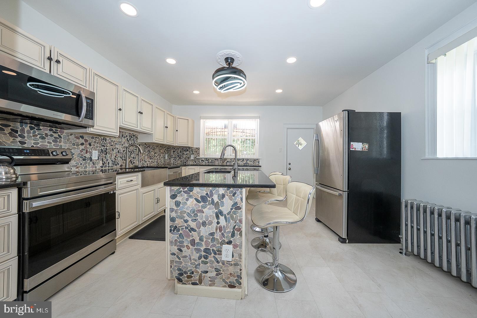 Welcome to this beautifully renovated corner three-bedroom/1.5 bath home with private parking, ideally situated on a lovely block in Philadelphia’s desirable Germantown neighborhood. This impressive residence combines modern updates, abundant natural light, and exceptional living space throughout. A large gated front porch provides the perfect setting for relaxing, entertaining, or enjoying the neighborhood atmosphere. Inside, the bright and airy open-concept living and dining areas feature stylish flooring and a seamless flow into the stunning chef’s kitchen. Thoughtfully designed, the kitchen boasts beautiful cabinetry, sleek granite countertops, stainless steel appliances, and a spacious center island ideal for cooking, gathering, and everyday living. Just beyond that, a large rear deck offers the perfect outdoor retreat for dining, entertaining, or simply unwinding. An elegant staircase leads to the second floor, where you'll find three generously sized bedrooms with excellent closet space and a renovated full bathroom. The fully finished walkout basement provides valuable additional living space and includes a convenient powder room, generous storage, and endless possibilities for a family room, home office, gym, or guest area.  Additional features include beautiful fan light fixtures and brand new paint throughout. This move-in-ready home offers comfort, style, and convenience. Ideally located near shopping, dining and public transportation. This exceptional Germantown property is ready for its next owner. Just unpack and enjoy!