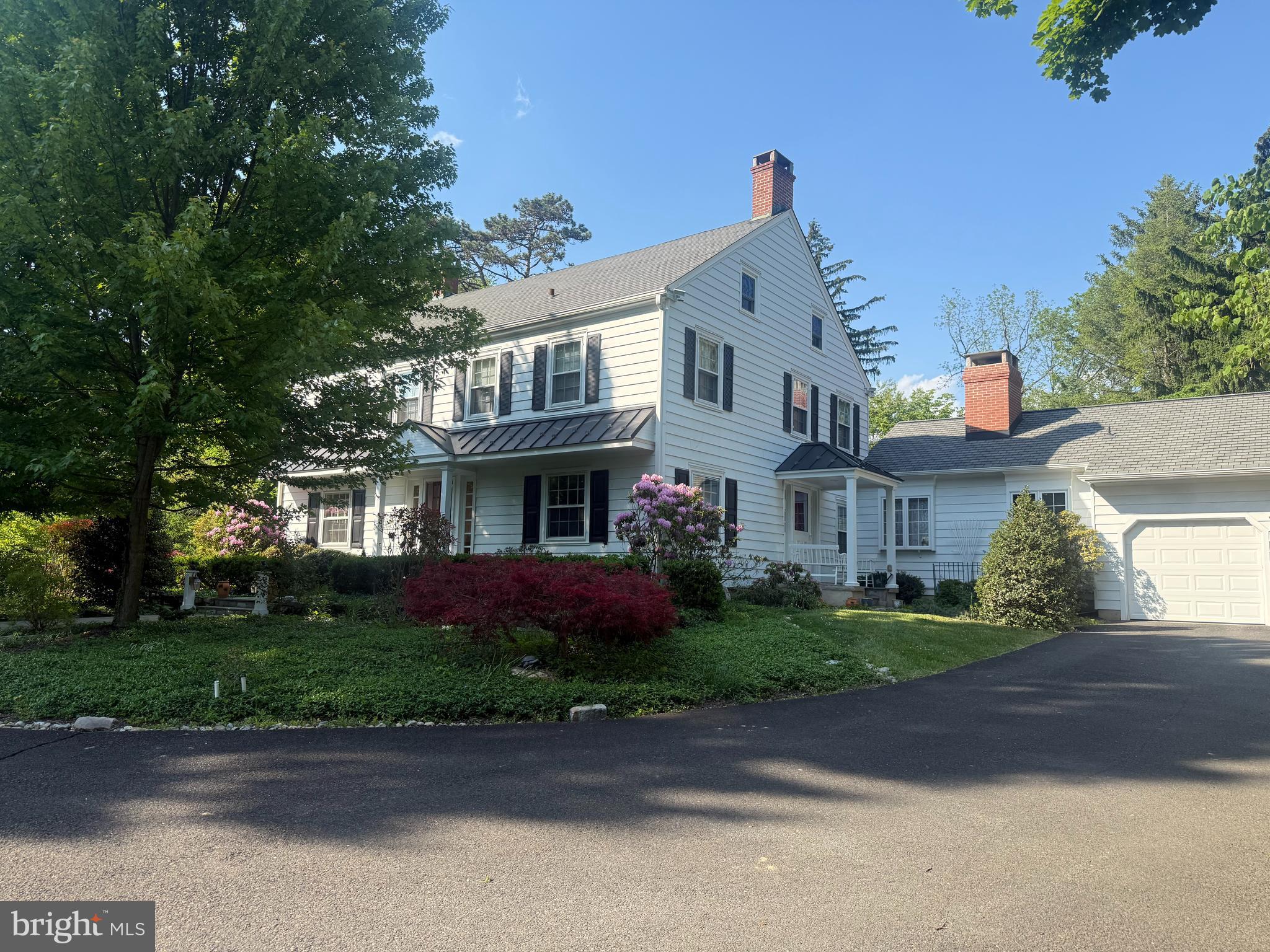 Nestled on a beautifully landscaped 1.26-acre corner lot in the coveted Pebble Hill neighborhood, this stately residence, affectionately known as Pebble Hill Manor, was built in 1938 and is located just minutes from the heart of Doylestown Boro. Reminiscent of a classic manor house, the home blends timeless architectural character with quality craftsmanship and thoughtful updates by its current owner, a retired custom home builder. Renowned Architect Oscar Martin contributed to some design elements of the original home.
A gracious center hall entry opens to an oversized foyer and warm, inviting living spaces. The formal living room features hardwood floors, custom built-ins, and a corner wood-burning fireplace. Nearby, a handsome home office/den showcases a fireplace with genuine Moravian tile and custom millwork, with a convenient side entry ideal for those who occasionally meet with clients.
The formal dining room is generously sized and filled with natural light from two large windows. Opposite is the efficient U-shaped kitchen offering cherry cabinetry, black granite countertops, stainless-steel appliances, and a practical layout. A passthrough connects to the stunning rear family room addition featuring deep windowsills, custom cabinetry, a striking stone fireplace, and a charming window seat. An informal dining area near the kitchen opens to a screened patio—perfect for summer evenings.
Beyond the family room is a mudroom with exterior access, a separate laundry room, and entry to the oversized three-car garage with a second-level storage or workshop area. The second floor offers four spacious bedrooms with hardwood floors, ample closets, and two full baths, including a Jack & Jill bath between the front bedrooms. A staircase leads to the third floor, which features two additional large rooms, a full bath, and abundant storage.
A partial basement houses the utilities and provides additional storage. Oil-fired hot water heat warms the home through original radiators, with cast-iron baseboards in the addition, while central air conditioning ensures summer comfort.  Generac generator provided in case of power outage.
Outdoors, the landscaped grounds feature seasonal plantings, mature trees, a bluestone walkway to the front entrance, and an expansive bluestone patio ideal for entertaining. A backyard shed with a newer cedar shake roof provides garden storage, while a semi-circular driveway from Pebble Hill Road to Christopher Lane offers abundant parking and an elegant approach.
A brand new traditional in the ground septic system (for a 6 bedroom residence) has been approved and will soon be installed.