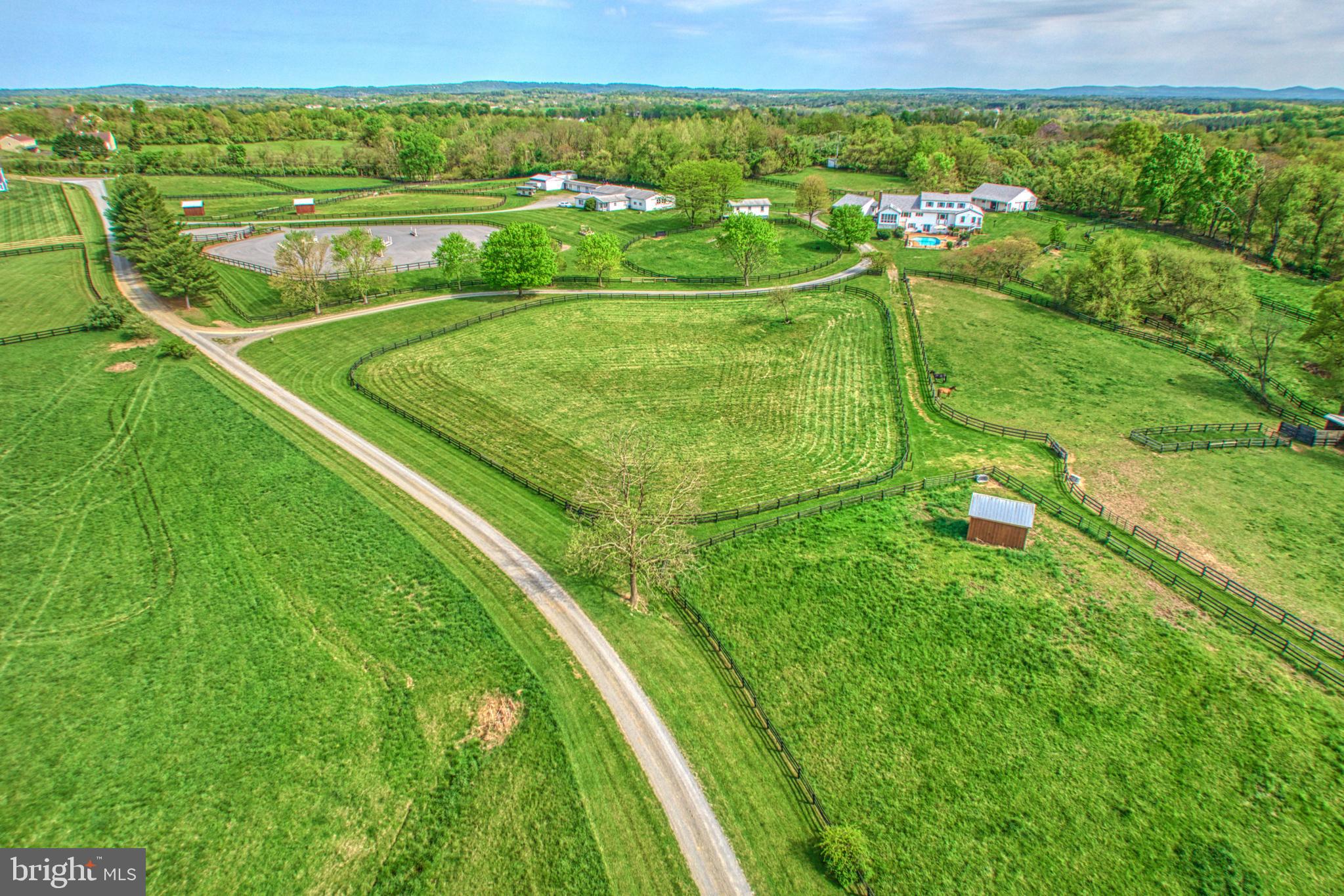 HORSEMAN’S DREAM FARM
This rare opportunity is just four miles from downtown Purcellville and within 40 minutes of Dulles irport. Both Loudoun Golf and Country Club and Stoneleigh Golf Club are withina 10 minute drive. This lovely 26 acre property offers the perfect get away with a peaceful setting. Stunning mountain views. Nestled at the foot of the Blue Ridge Mountains in Round Hill, VA. Providing small hometown living, all the amenities of city life, an abundance of outdoor activities and NO HOA.  The property has an expansive 4 bedroom, 4.5 bathroom custom built home with three finished levels, professionally renovated in 2024. The formal living room has a wood burning fireplace and bay window framing the mountain views. Plenty of room for family and friends. Just off the formal living room is the formal dining room. Stunning bay window and freshly refinished hardwood floors, this home is completely heartwarming. Next to the dining room is the brand-new eat-in kitchen with pantry and plenty of storage. Large island invites you to sit and mingle with the chef of the house or have a seat at the farm table and enjoy the views from yet another large window. The kitchen and eating area open into the family room with vaulted ceiling, hardwood floors and a grand stone fireplace. Just off the family room is the office with windows on 3 sides for panoramic views of the mountains. The swimming pool provides a wonderful view of the mountains and was currently updated.  Four barns – one is  an 11 stall center aisle with wash-stall , tack room , bathroom, washer/dryer, the other a 6 stall center aisle barn, with a tack-room, wash-stall, hay loft. Large Hay barn and separate 6 stall shed row barn.  Large all weather riding arena, 71 ft. round pen. Large equipment shed, 16 double fenced paddocks with electric and water. Seven loafing sheds. Two separate income producing rental units, a charming detached cottage and a two bedroom apartment attached to the Main 11 stall barn. This is a successful professional horse facility.