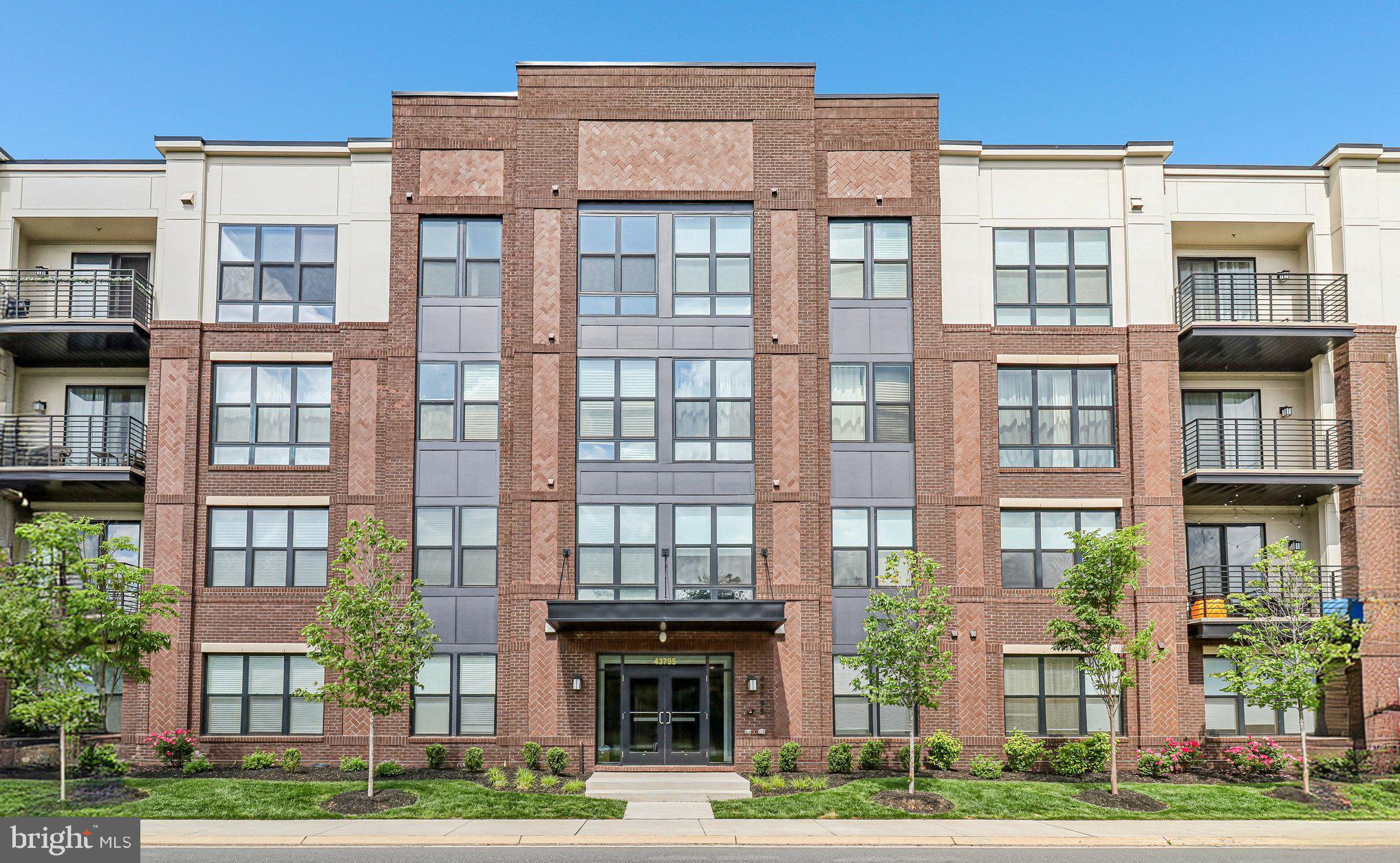 Exceptional one-level condo offering 1,804 square feet of elegant, contemporary living. From the moment you enter, you’ll fall in love with the expansive sun-filled living and dining room combination featuring wood floors, a fireplace, and a wall of windows with access to a private balcony. The entire unit overlooks the large community green space with play area, fire pit, grills, and outdoor seating. The gourmet kitchen is perfect for entertaining and showcases top-of-the-line upgrades throughout, including a large island that enhances the spectacular modern design. The spacious primary suite, located on the left side of the home, features windows on two sides, a walk-in closet, and a luxurious primary bath with a stunning oversized shower and double vanities. The large secondary bedroom on the opposite side of the residence is equally impressive, offering excellent privacy and space. A separate den provides the perfect flex space for a home office or additional sitting area. Separate storage just off the hall is an added bonus. This secure building with an elegant lobby and elevator is a rare find. The unit has a private 1 car garage with electric vehicle charging capacity and a private driveway for a 2nd designated parking spot. Central wireless access point and wired connections for exceptional media access. Affordable fees. Exceptional location near shopping, dining, and approximately one mile to the Metro.