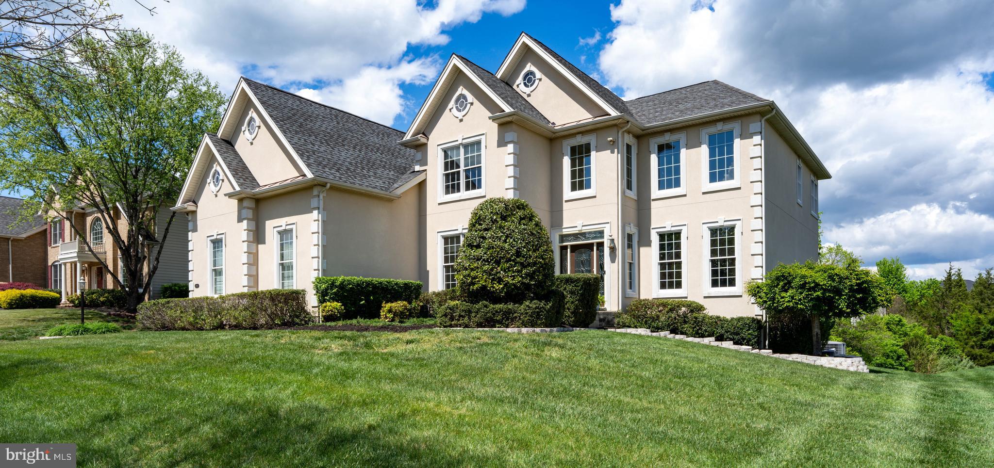 Elegant design, exceptional entertaining spaces, and a private half-acre wooded lot come together in this stunning Dalton Provincial, perfectly positioned on a quiet cul-de-sac in one of Northern Virginia's most sought-after country club communities. A stately stucco exterior, architectural window details, soaring two-story foyer, and dramatic living room create an impressive first impression. The Palladian kitchen is a true centerpiece, featuring premium Monogram appliances, a commercial-grade 6-burner range, three ovens, granite countertops, upgraded cabinetry, prep sink, pot filler, beverage refrigerator, and a large center island. The kitchen opens seamlessly to the spacious family room with a striking stone gas fireplace, built-in bar, and wall of windows, creating the perfect setting for everyday living and entertaining. A screened porch extends the living space outdoors and overlooks peaceful wooded views. A private main-level office, 3-car side-load garage, and oversized driveway add convenience and functionality. Upstairs, the spacious primary suite offers two walk-in closets and a spa-inspired bath with a jetted tub and oversized double shower. Each secondary bedroom features its own walk-in closet. The finished walkout lower level offers a large rec room, TV/lounge area, full bath, abundant storage, and the potential for a legal fifth bedroom thanks to full-size windows. Additional highlights include hardwood floors, central vacuum, irrigation system, new bedroom carpet (2026), family room carpet (2023), water heater (2023), dishwasher (2022), and freshly painted office and lower level. Enjoy Dominion Valley Country Club's exceptional amenities, including an Arnold Palmer Signature golf course, clubhouse, Sports Pavilion, indoor and outdoor pools, tennis and basketball courts, playgrounds, trails, fishing ponds, and award-winning schools.
