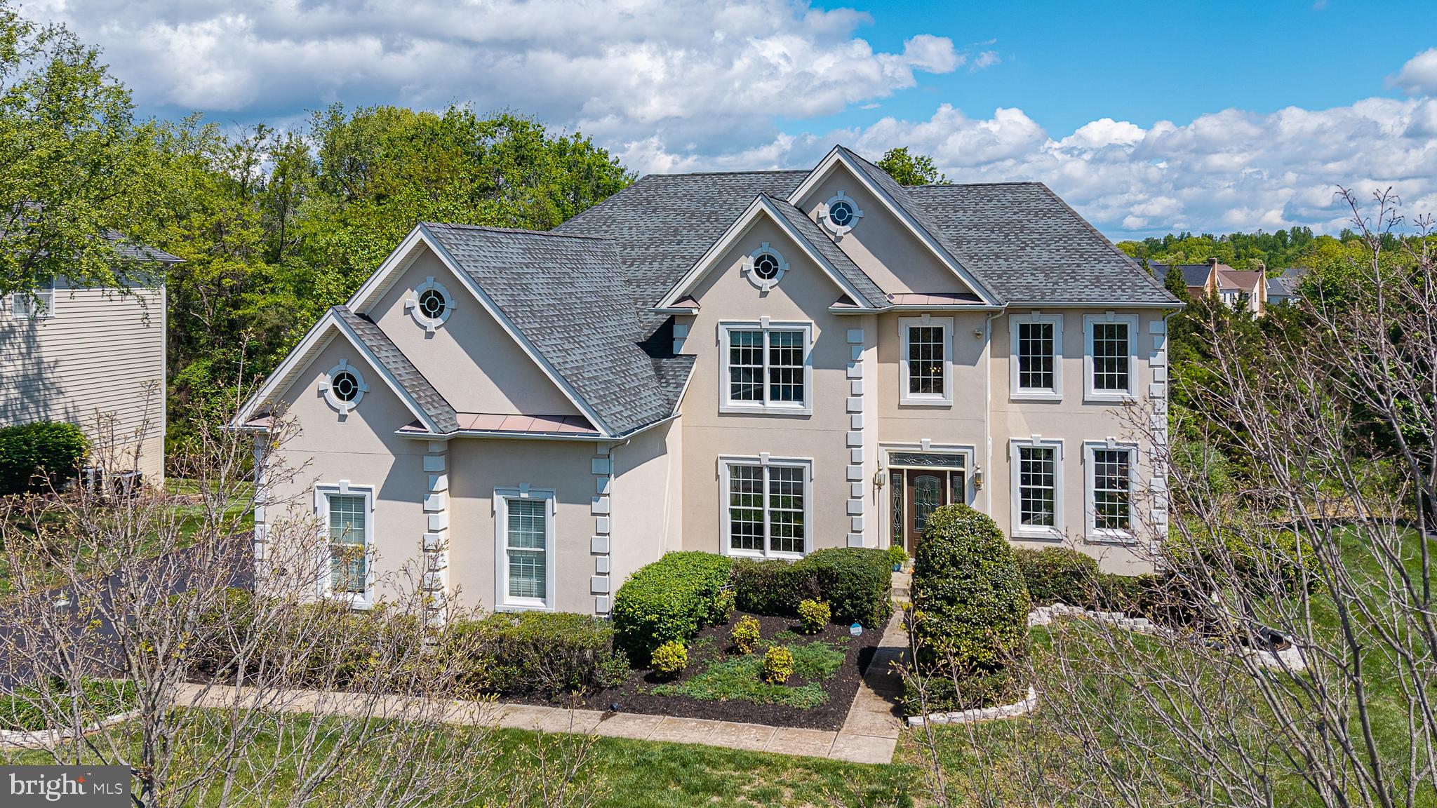 Best value in DVCC! Elegant design, exceptional entertaining spaces, and a private half-acre wooded lot come together in this stunning Dalton Provincial, perfectly positioned on a quiet cul-de-sac in one of Northern Virginia's most sought-after country club communities. A stately stucco exterior, architectural window details, soaring two-story foyer, and dramatic living room create an impressive first impression. The Palladian kitchen is a true centerpiece, featuring premium Monogram appliances, a commercial-grade 6-burner range, three ovens, granite countertops, upgraded cabinetry, prep sink, pot filler, beverage refrigerator, and a large center island. The kitchen opens seamlessly to the spacious family room with a striking stone gas fireplace, built-in bar, and wall of windows, creating the perfect setting for everyday living and entertaining. A screened porch extends the living space outdoors and overlooks peaceful wooded views. A private main-level office, 3-car side-load garage, and oversized driveway add convenience and functionality. Upstairs, the spacious primary suite offers two walk-in closets and a spa-inspired bath with a jetted tub and oversized double shower. Each secondary bedroom features its own walk-in closet. The finished walkout lower level offers a large rec room, TV/lounge area, full bath, abundant storage, and the potential for a legal fifth bedroom thanks to full-size windows. Additional highlights include hardwood floors, central vacuum, irrigation system, new bedroom carpet (2026), family room carpet (2023), water heater (2023), dishwasher (2022), and freshly painted office and lower level. Enjoy Dominion Valley Country Club's exceptional amenities, including an Arnold Palmer Signature golf course, clubhouse, Sports Pavilion, indoor and outdoor pools, tennis and basketball courts, playgrounds, trails, fishing ponds, and award-winning schools.