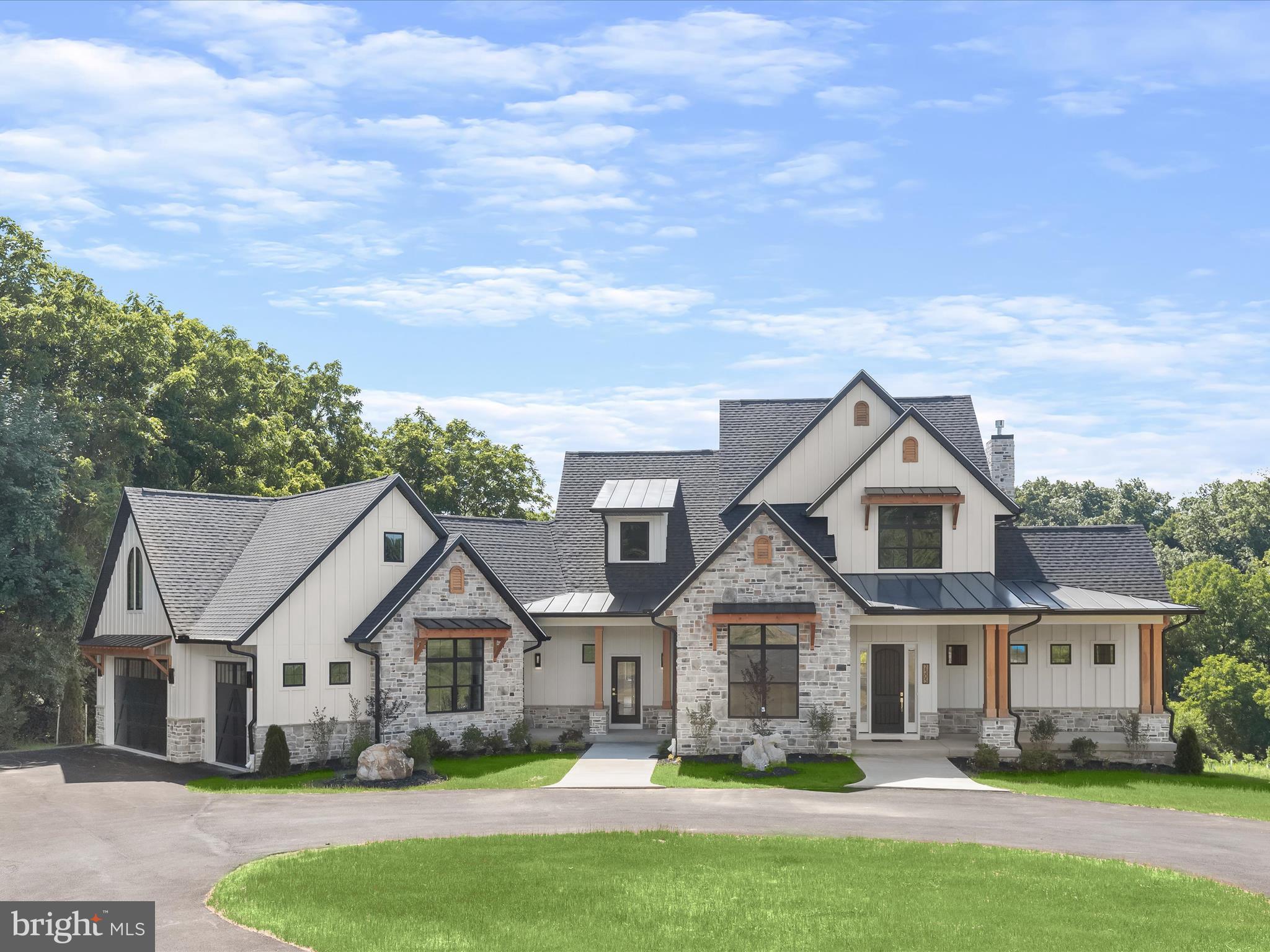 With up-to-the-minute style, finishes and modern capabilities, this new construction Craftsman-style home offers the perfect blend of energy efficiency, spatial quality and a comfortable modern aesthetic. The exterior finishes nod beautifully to the Craftsman style with natural stone, vertical Hardie plank, stained square columns and deep bracketed eves (now “called eyelashes”) with standing seam metal. There is deep sensitivity to massing as the gables, porches, coupled columns and eyelashes combine to make all four sides of this home aesthetically pleasing.

A gracious circular drive stops at two sidewalks embellished with creative landscaping that lead to the front door and the secondary door. Inside, a two-story foyer opens to reveal the lightly stained hardwood floor, curved staircase, and rail with a fresh natural feel. The smooth matte hardwood floors and natural vibe continue throughout the entire main level, unfolding first into the dining room delivering an eye-popping wood plank ceiling and a generous service wet bar. The extended foyer is sided by a seating alcove defined by the sweeping curve of the stair and a dramatic modern trim accent wall.  Special moments happen at every turn including an oversized lighted art niche opposite the powder bath and adjacent Study streaming light from double windows, clerestory windows and an atrium door to the wrap around covered deck. 

With rustic charm, the beamed ceiling in the family living room aptly offers warmth, depth and texture to the heart of the home alongside a cozy gas fireplace clad in stone that remembers the stone exterior.  Entertaining is easy in the open plan design that showcases the gourmet chef’s kitchen with an oversized peninsula and breakfast bar, and trending quartz waterfall edge where guests can converse while the cook creates snacks and meals behind a commanding center island. Wrap-around contrast cabinetry alternates with fresh white cabinetry in keeping with the soft neutral vibe in the overall design. A complete suite of luxury white Café professional appliances are accented with brushed gold hardware pulls and oversized pendants that take full advantage of the open space. The floor plan seamlessly flows into the breakfast area where an atrium door invites guests outside to a low maintenance wrap-around composite dining deck.

First floor living is a hallmark of this comfortable home offering lifestyle flexibility featuring a main level owners suite, large spa like bath and a well-appointed walk-in wardrobe closet. Completing the main level is the laundry room, second entry, arrival room with built-in cubbies, and a back stair to the upper-level bonus room that takes full advantage of the vaulted ceilings.  There are a total of four bedrooms that include the main level owner’s suite, and three more in the bedroom wing of the upper level. 

Details, details and more details are expressed with many unifying elements from the natural stone, black window frames, the contrast paint color, the warm wood stain, and stylish lighting, this home has the perfect blend of energy efficiency, spatial quality and a comfortable modern aesthetic.  Come home to a brand-new luxury home and a very special lifestyle!