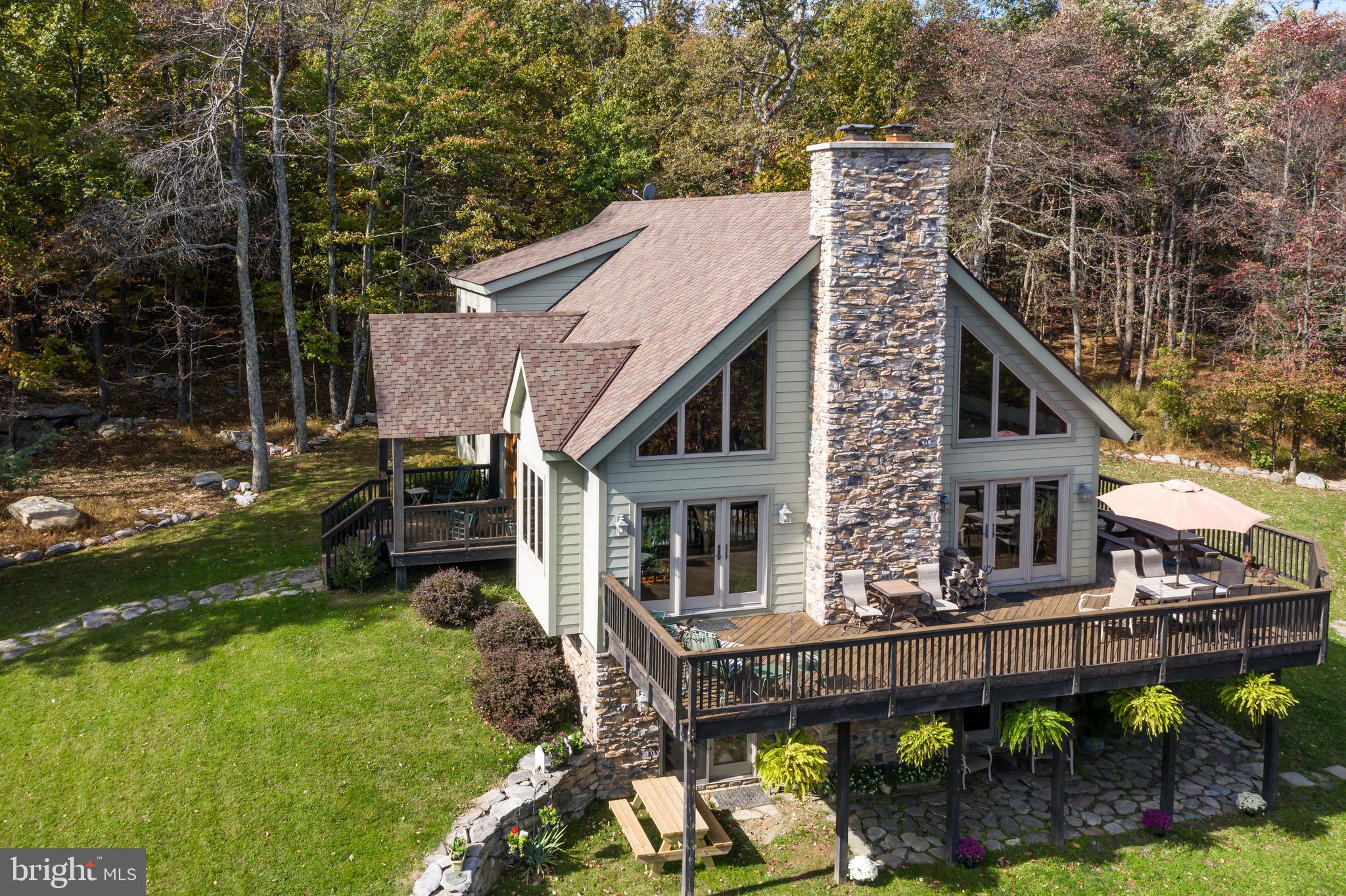This dazzling mountain retreat sits on 25.31 forest-enclosed acres attached to the Appalachian Trail, on an east facing mountainside, providing panoramic views from a huge wrap around deck. The 4000-square-foot custom built post and beam home currently serves as a residence, a bed-and-breakfast, retreat venue and a hostel for hikers, providing a warm and welcoming organic atmosphere for family, friends, and adventurers.The stone walkway, created from rocks gathered on site, leads to the hand-carved wood doors on the covered front porch, whose post-and-beam design is echoed on the interior in grandiose fashion. Earthy hardwoods cover the floors and the high, angled ceilings of the main living area, which combines the entryway, living room, dining area, the beautifully handcrafted kitchen and elevated loft into one communal space. On the east-facing wall, a stone fireplace stretches to the ceiling and is flanked on either side by large windows and all-glass doors, offering splendid views of the Loudoun Valley   especially at sunrise. This level houses two bright sunny bedrooms   and a special claw foot tub bath with antique vanity sink.The upstairs loft overlooks the great room and serves as a library, sitting and game space with room to host musicians for entertaining. Behind the loft sits the master bedroom retreat, with large sitting area, a private deck under the trees and a luxurious master bath, complete with a glassed-in shower and spacious water closet.On the bottom level is a large, entertainment-ready recreation space with an all wood kitchenette and hand crafted half log bar, all centered around a second stone fireplace and wood burning stove, with more large windows and glass doors for walk-out access to the below-deck stone patio. The bedroom and extra room on this level can be used for multiple beds/bunks or office and work spaces. This level is fully handicap accessible, including the bath with roll in shower and a portable entrance ramp from ground and driveway level.Outside   walk on multiple paths through the woods to sitting area rocks, to rock outcroppings, the Appalachian Trail, and a large campfire ring complete with natural logs for sitting and tent pad for camping.Finally, the owner can either rent out or house additional guests in the 900+ sqft  finished full apartment space above the spacious three-car garage - beautiful enough for the owners living space!With cozy amenities on the inside and wildlife-filled beauty on the outside, this setting is remote enough to be peaceful and serene, while still in close proximity to conveniences, historic Harper s Ferry, Revolutionary and Civil War sites, and recreational activities   This Hillsboro home could be your very own idyllic mountain retreat today!