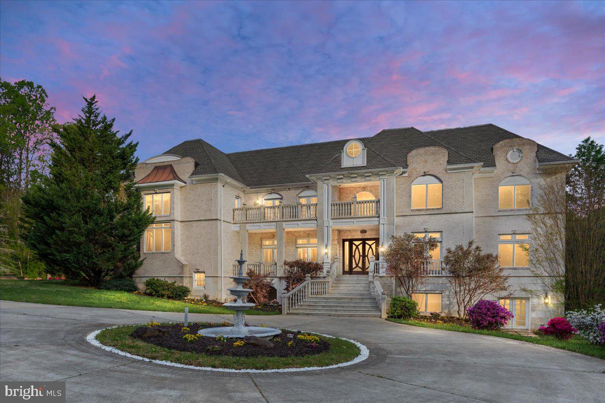 This extraordinary home manages to do the impossible: it offers over 17,000 square feet of architectural brilliance while maintaining incredible warmth and intimacy. While the scale is undeniably grand, the floor plan is a masterclass in human-scale design, prioritizing an unhurried flow and everyday livability. From the moment you arrive, the imported Spanish railings and brick-and-granite façade establish a sense of enduring quality, yet the layout ensures that the first impression is as inviting as it is stately.

The brilliance of the interior lies in its intentional proportions. While the formal spaces command attention with soaring 20-foot ceilings and towering walls of glass, the home always feels welcoming. Rich Brazilian Cherry hardwoods anchor each room, creating a grounded atmosphere that beautifully balances the dramatic volume of the formal living and family rooms. Here, the architecture invites natural light to fill the space, ensuring that even the most impressive rooms feel airy and inherently comfortable.

A grand, beautiful office overlooking the front yard greets you just off the foyer, serving as an inspiring workspace before transitioning into the deeper wings of the estate. Chief among these private quarters is the primary suite—a true sanctuary spanning over 1,700 square feet to offer an exclusive wing for total decompression, complete with a dedicated sitting area and a spa-inspired bath outfitted with a steam shower, dual vanities, and a deep jetted tub.

At the heart of the home, the kitchen and family room transition seamlessly for a layout designed for true connection. Though equipped with premium appliances for serious entertaining, the space remains centered on daily life, featuring a generous breakfast room and a built-in coffee station for slow mornings. Thoughtful touches like a fireplace in the mudroom—one of five throughout the estate—ensure that even utilitarian transitions feel cozy. This wing also includes a dramatic two-story library, topped by a dedicated art gallery that keeps the home’s creative spirit visible and accessible.

The upper levels prioritize the luxury of space and privacy, connected by extra-wide hallways that make moving through the home feel effortless. Each secondary bedroom is a full suite with its own private bath, and three feature granite balconies for private outdoor escapes. Practicality is woven into this grand design, with laundry facilities on all three floors and an elevator to simplify the logistics of daily life.

The lower level defies expectations of a basement, offering a bright, open-concept wellness and entertainment hub that feels like an exclusive private club. A 960-square-foot professional gym anchors the wing, sitting alongside a full spa with a sauna and steam shower. With direct access to the private inground pool, the transition between indoor wellness and outdoor recreation is seamless. Between the wine cellar, media room, and multiple recreation spaces, the floor plan provides an intuitive flow for both large-scale hosting and quiet family indulgence.

Perhaps the most comfortable aspect of this estate is the peace of mind provided by its forward-thinking infrastructure. A sophisticated geothermal heating and cooling system paired with solar panels allows the home to operate with incredible efficiency, keeping average monthly utilities under $300. It is a rare achievement to find a residence that offers the grandeur of a palace with the manageable footprint and sustainable ease of a modern home. This is a generational statement built for legacy, where every square foot is designed to help your life unfold with total ease. *** Fully Inspected Elevator Shaft in Place - Elevator to be installed prior to settlement