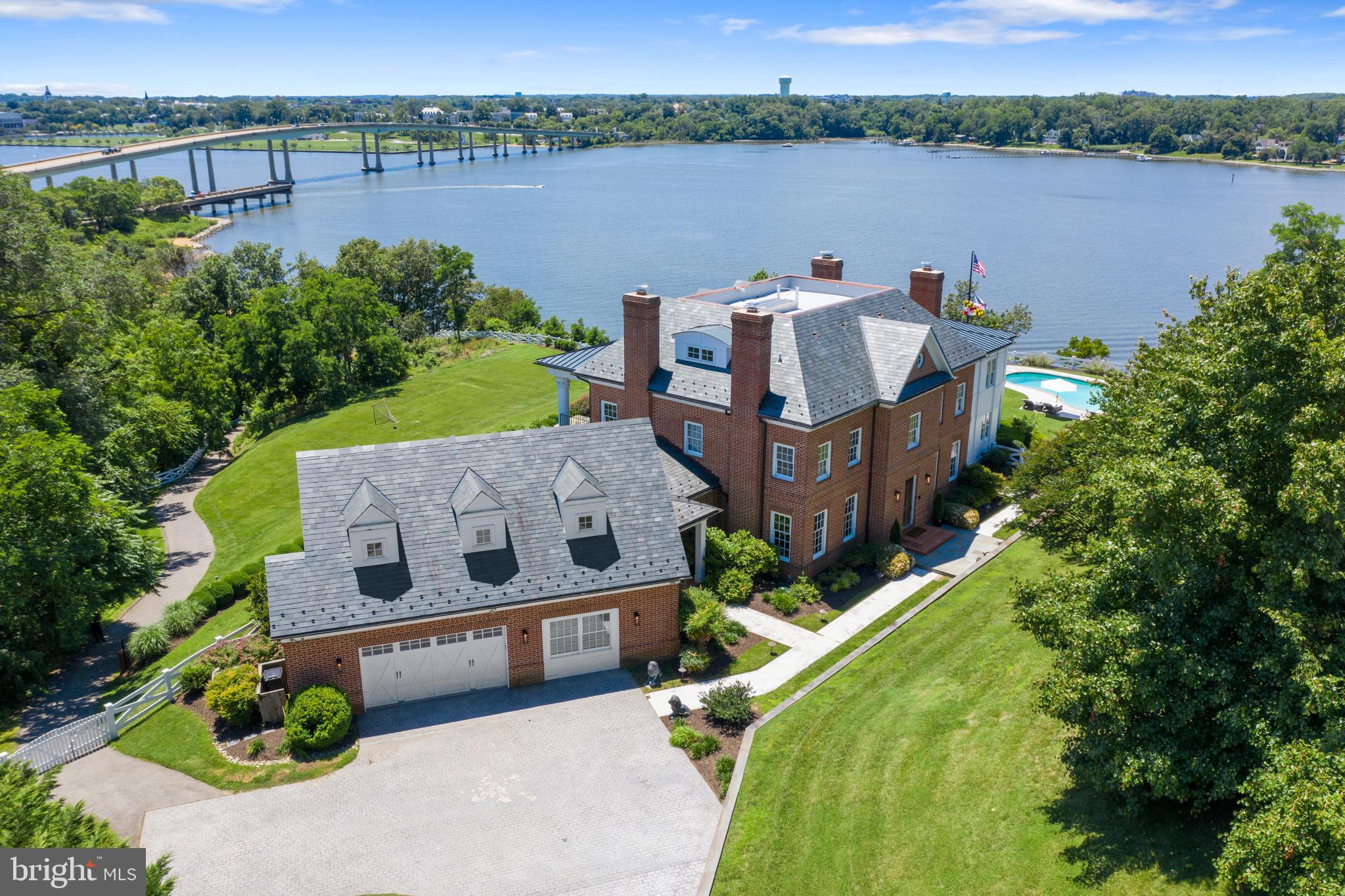 A Stunning transformation! This iconic Annapolis waterfront estate has been meticulously updated with no detail overlooked.  Built in the Coastal-Tidewater style, this home was crafted to capture the commanding views of the Severn River and beyond.  The brick exterior and dramatic, formal columns add to the grand appeal of the home.  New heart of pine flooring with a light pickled oak finish was installed throughout the entire home lending a "sea- side Hamptons" vibe to the interior. A grand, mahogany staircase welcomes you in the front entry hall. To the left of the front hall is a formal dining room and to the right is the study.  Each room is entered through french doors and has a wood burning fireplace with custom carved marble mantle.  The kitchen is a chef's delight. Thoughtfully laid out and outfitted with viking appliances, it is a true gathering space.  The oversized, soapstone island allows guests to mingle and chat up the host while enjoying the views.  A custom, hand-cut, subway tile laid in a herringbone pattern is a dramatic accent behind the custom hood vent and viking 6 burner range.  A farm sink, dual dish washers, ice maker, warming drawer, pot filler and custom rattan-basket globes complete the "must haves" of any high end designer kitchen.
Moving down from the kitchen is the family room with two-sided, wood burning fireplace with custom, hand carved marble mantle.    On the other side of the two way fireplace is what the owners affectionately refer to as 'The River Room.' A comfortable yet elegant space with panoramic views of the Severn River and swimming pool, a full bar with beverage fridge and sink, a full bath also accessed from the pool deck through a set of custom wood, exterior doors.  On level two you will be greeted by a set of french doors opening to the second level lounge and game room...or whatever you wish the room to be...including a bedroom.  This room has its own balcony with incredible views and full bath.  To the end of the hall on the left is a spacious bedroom suite with full bath and dual closets. To the end of the hall on the right is a full laundry room and just beyond that you arrive at the waterside owner's suite.  As you come in the suite to your left is a dedicated shoe closet and to the right is a fully renovated spa bath. Done in soft white and grays with a mat finished marble tile floor, custom pine vanities with white/gray marble counters, a massive steam shower with custom, hand cut white subway tile and a gorgeous hexagon marble floor. There is a free standing soaking tub with views of the pool and water, a separate water closet equipped with a bidet and a gorgeous, wood beaded, bohemian style chandelier.  The main living space in the owner's suite is surrounded by views of the river, pool and grounds. While relaxing in bed you will notice each window has a different view...one of the newly restored Navy Chapel Dome, The Capital Dome and St. Mary's Spire. Two custom closets, a beverage station/wet bar and waterside balcony add to the appeal and make this room in the home rival any 5 star resort. Continue up to the third level where you will find an additional recreation room ideal for t.v, crafts and studies and two bedrooms with a full hall bath. Then it is up  the stairs leading to the roof top deck - with a fully secure, safety door and new roof. The basement houses a recreational area, laundry, home gym and bonus room. From the side entry hall you will find a main level bedroom suite and an over-the-garage guest suite.  Enjoy the sprawling lawn, take a swim in the waterside pool then a ride in the tram down to the deep water pier complete with light/electric and 4 lifts. Perhaps you prefer to take the private drive down to your private beach? Launch a personal watercraft, swim or fish...the possibilities are endless.  Arrive downtown Annapolis in under 10 minutes and to Baltimore/DC in 30-35. You'll be hosting the next Blue Angels soiree here...and many more to come!