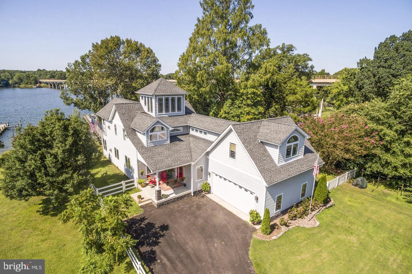 This exceptional custom home on a double waterfront lot offers nice privacy and premium boating access just minutes from the Patuxent River, Chesapeake Bay, and Solomons Island. The exterior features a 149-foot  pier with three  slips, a jet ski lift, and accommodation for a large sailboat(6-foot draft), alongside beautifully landscaped grounds, waterview porches and a plumbing-ready waterside shed.
An impressive 8-foot stained-glass front door opens to a dramatic two-story foyer and open floor plan featuring 10-foot ceilings and radiant-heated beautifully refinished oak floors. The gourmet kitchen boasts custom cabinetry, granite countertops, premium Wolf and Bosch appliances, new refrigerator, stylish backsplash and an expansive breakfast bar. It flows seamlessly into a dining room with loads of natural light and breathtaking water views . Also a cozy family room equipped with a gas fireplace and custom built-ins. A main-level guest bedroom, full bath, and mudroom complete the first floor.
Upstairs features luxury vinyl flooring throughout and an extra-large primary suite featuring cathedral ceilings with exposed barn beams, a gas fireplace, a large private waterfront balcony, and a spa-inspired bath complete with a unique heating stove, whirlpool tub, and custom walk-in shower. A second spacious bedroom and laundry room complete this level. A stunning spiral staircase leads to the unique tower solarium, offering panoramic creek views perfect for a meditation space or home office.
High-end mechanicals include an efficient Buderus furnace (powering domestic hot water and the radiant floors across the main level and the oversized, heated 2-car garage/workshop), a 13kW Generac whole-house generator and central vacuum!
