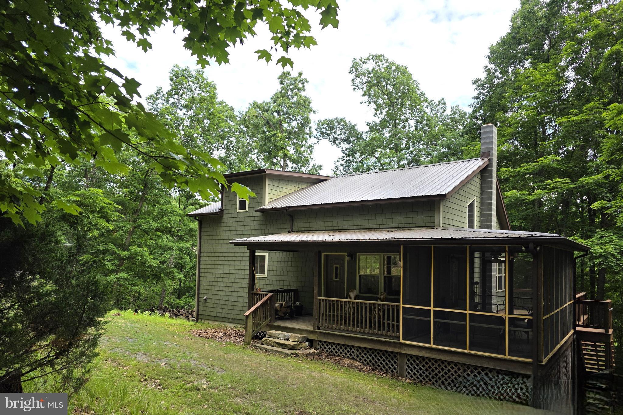 Located minutes from the quaint town of Franklin in the Buck Ridges community, this charming cabin-style home offers a perfect blend of comfort and nature. Built in 2008, with sturdy construction of 6" walls, this detached residence boasts 3 spacious bedrooms and 3 bathrooms, providing ample space for relaxation and privacy. The open floor plan seamlessly connects the living and dining areas, enhanced by warm wood floors and a cozy Jotul wood stove, creating an inviting atmosphere for gatherings. The galley kitchen is well appointed with natural light and ample counter space. Enjoy the convenience of a main floor laundry off of the galley kitchen and a primary bedroom with a walk-in closet and en-suite bath, ensuring everyday ease.  Upstairs, you'll find a cozy reading nook with a wall of bookshelves. From there, you'll enter a bedroom w/seating area and en-suite flooded with natural light and lots of unique touches. The fully finished basement also has plenty of natural light and features another living space with adjoining bonus room. Down the hall you'll find a workshop/utility area, bath and the downstairs bedroom. From the basement, you can walk out to the beautiful stone patio where you can sit and enjoy the views of nature and passing wildlife.  The cabin's  water supply is from a wonderful Spring located in the development. This 11. 54 acre property is beautifully secluded near the end of dead end road, backing to trees and offering a peaceful rural setting, but the newly installed underground fiber optic cable will keep you connected if you need to get a little work done while you're here. There are also additional outdoor spaces to enjoy, including a screened-in porch and adjoining deck, inviting you to relax and unwind.   Experience the harmony of nature and modern living in this delightful home, where every detail has been thoughtfully crafted. It's the perfect retreat from the hustle and bustle, yet still close enough to enjoy local amenities where you can enjoy swimming, bowling, our popular coffee shop, drive-in movies, fishing and hiking. Just a short 30 minute drive West will take you to Seneca Rocks Recreation area where you can enjoy rock climbing, hiking, caverns, etc. Drive an hour to the East and you can be in Harrisonburg, VA near Interstate 81 for ease of travel. Access is dirt/gravel road.   Some covenants & restrictions apply.