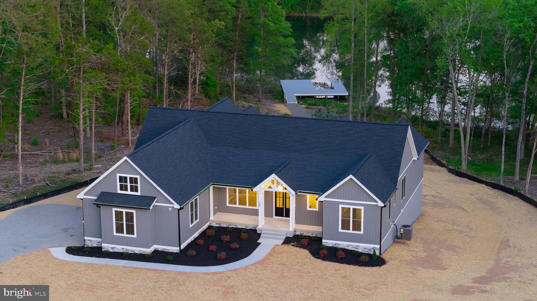 Experience elevated lake living in this brand new waterfront home on the private side of Lake Anna, Virginia, where luxury, comfort, and craftsmanship come together seamlessly. Built by award-winning Built Right Homes and nearing completion, this stunning Craftsman-style residence offers over 5,500 square feet across two beautifully designed levels. From the moment you arrive, the impressive 8-foot double front doors set the tone for what’s inside. Step into an open, light-filled floor plan featuring 9-foot ceilings, premium Mohawk LVP flooring, and a striking gas fireplace with custom built-ins. The gourmet kitchen is a true centerpiece, complete with a large island, quartz countertops, tile backsplash, stainless steel appliances, a 5-burner gas cooktop, double wall ovens, a farmhouse sink, and an oversized walk-in pantry designed for both function and style. With 6 bedrooms and 4.5 baths, there is space for everyone. The main level showcases two lakeside primary suites, each with its own private bath featuring beautifully tiled showers—one with a soaking tub—and both offering direct access to the deck overlooking the water. The main level also features two additional bedrooms that share a Jack-and-Jill bath, a convenient mudroom/laundry room and a half bath. The finished walkout basement expands your living space with a large family room, recreation area, two additional bedrooms, and a full bath. Plus, an extra 1,000 unfinished square feet offers endless possibilities—create a home theater, gym, or additional living space tailored to your needs. The exterior is just as impressive, featuring board and batten vinyl siding, 6-inch black gutters, and a partially covered back deck with a gas grill hookup—perfect for entertaining. Enjoy peaceful lake views from your level backyard, ideal for adding a pool, and take full advantage of your private dock with a sun deck already in place. Situated on a 1.5-acre lot in Compass Cove, Lake Anna’s newest subdivision, this home offers both privacy and convenience, just minutes from groceries, local dining, and Elk Creek Country Store. Whether you're cruising the lake, hosting unforgettable weekends, or maximizing income in this short-term rental friendly community, this is your chance to fully embrace the Lake Anna lifestyle—fun, relaxation, and memories all in one place.