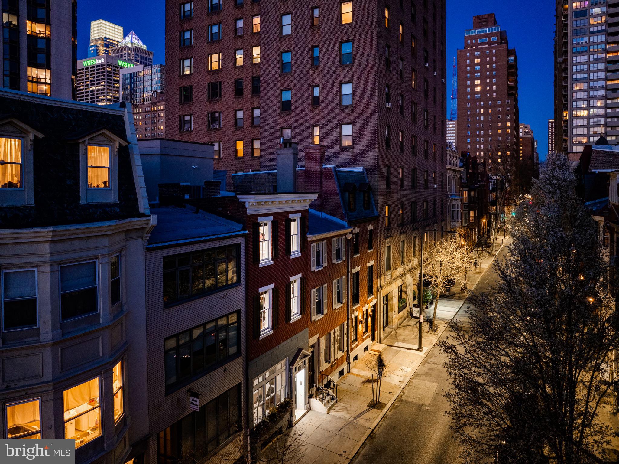 A 4 bed + gym, 5.5 bath contemporary townhouse only 1.5 blocks from Rittenhouse Square and with 2 car garage parking! Be prepared for a “WOW” behind the historic (Circa 1800) facade.

Open into the bluestone foyer and entry hall that dazzles with over 14 foot ceilings and an amazing, one-of-a-kind handcrafted centerpiece sculptural staircase that is both an architectural design element and a vehicle for spreading light throughout the home via 4 tubular skylights. Perhaps the most impressive and unique space in this home is the entertaining hub.

On the 3rd floor, which offers seamless indoor & outdoor living you'll enjoy a private deck oasis wrapped with planters (irrigated), a clear exposure of the skyline, BBQ with built-in gas line and a retractable awning (perfect for al fresco dining) If you enjoy entertaining or cooking you’ll love the modern kitchen with updated appliances, Snaidero Italian cabinetry, granite black leathered countertops and backsplashes, massive windows (2 sides), vaulted ceilings, terrific prep space, double ovens, counter seating, and open flow to the dining, powder-room and grand living room. The living room runs the full width of the home (18 ft) and overlooks Locust St to the south. Amazing sun! Amazing light!

The impressive and luxurious primary suite located on the 2nd floor offers dual bathrooms (his & hers), a walk-through rainfall shower, a walk-in closet, an additional 19.5 linear feet of built-in closets and a large bed area with room for seating. Not many homes have a primary suite like this!

3 additional bedrooms; one on the 1st floor (now used as an office) with a full shared hall bathroom, an en-suite on the 2nd across from the primary suite and a super private en-suite on the 4th. Thoughtfully designed by owner-occupants for a multitude of lifestyles – this re-imagined townhouse offers elegant & gracious spaces, ultimate privacy for you and your guests and beautiful quality finishes throughout.

Bonus features: A 4 stop elevator (basement to 3rd floor) for supreme convenience, An additional room on the 1st floor currently used as a yoga room, a lot measuring 90 feet deep going street to street (Locust to Saint James), room for guest parking (3rd car) behind the garage, fully wired for sound/internet, intercom camera system (front door entry), water & air filtration and water softening systems and extensive storage.

The perfect size…. a manageable townhouse experience you’ve always wanted that is move-in-ready! A location rivaled by few – steps from the Square, Philadelphia’s best dining establishments, Central Business District and a quick walk to our renowned green spaces along the River.
