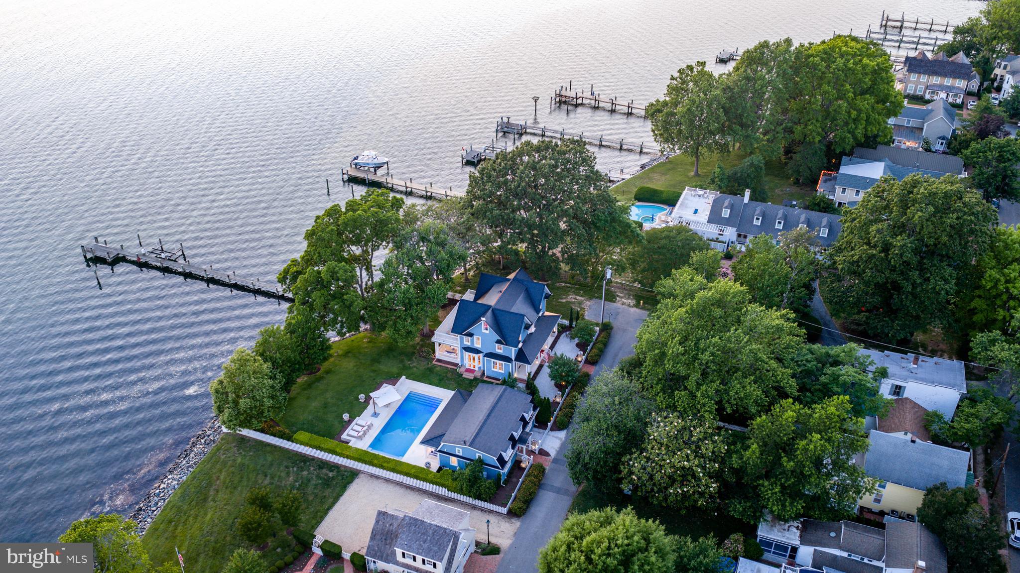 Perfectly positioned along the prestigious shores of the Tred Avon River, this extraordinary waterfront estate offers breathtaking water views from nearly every room and an unparalleled blend of luxury, craftsmanship, and cutting-edge sustainability.
Designed to embrace its spectacular setting, the three-level main residence features exceptional attention to detail throughout, including rich hardwood flooring, custom millwork, hidden built-in cabinetry, and exquisite finishes at every turn. A gracious main hallway draws your eye directly to the covered waterside porch, creating a seamless connection between the home's elegant interior and its stunning riverfront backdrop. The heart of the home is a chef's kitchen appointed with marble countertops, a spacious center island, and thoughtfully designed gathering spaces that flow effortlessly into the dining room and inviting sitting room with a fireplace. The second-floor primary suite serves as a private retreat, featuring access to its own waterfront balcony overlooking the Tred Avon River. The luxurious primary bath offers a beautiful tiled steam shower with water views, a dedicated vanity area, and an expansive custom walk-in closet with integrated laundry. Outside, an incredible overflow pool creates a resort-like setting where endless river views take center stage. Guests will enjoy complete privacy in the detached guest house, which includes a kitchenette and full bath. A detached one-car garage provides additional storage and convenience. Built with both comfort and efficiency in mind, the property showcases Tesla Solar Roof shingles on both the main residence and guest house, geothermal heating and cooling, radiant floor heating throughout the first and second levels, seven Tesla backup batteries providing power during outages, and elevator access serving the first and second floors. A rare offering in the heart of historic Oxford, 200 West Street represents waterfront living at its finest—where timeless elegance, modern innovation, and spectacular views come together in one unforgettable property. --- {Luxury & Special Features} Waterfront primary suite featuring a private balcony, rain shower, and steam bath | Chef's kitchen with two freezer drawers and built-in plate warmer | Continuous warm water circulation system throughout the home | Dedicated water pressure enhancement system | Elevator serving the first and second floors | Radiant floor heating throughout the first and second levels | Geothermal heating and cooling system | Tesla Solar Roof shingles on the main residence and guest house | Seven Tesla Powerwall backup batteries providing power during outages | Tesla electric vehicle charging station | Resort-style overflow pool overlooking the Tred Avon River | Electric retractable awnings | Detached guest house with kitchenette and full bath | Detached one-car garage