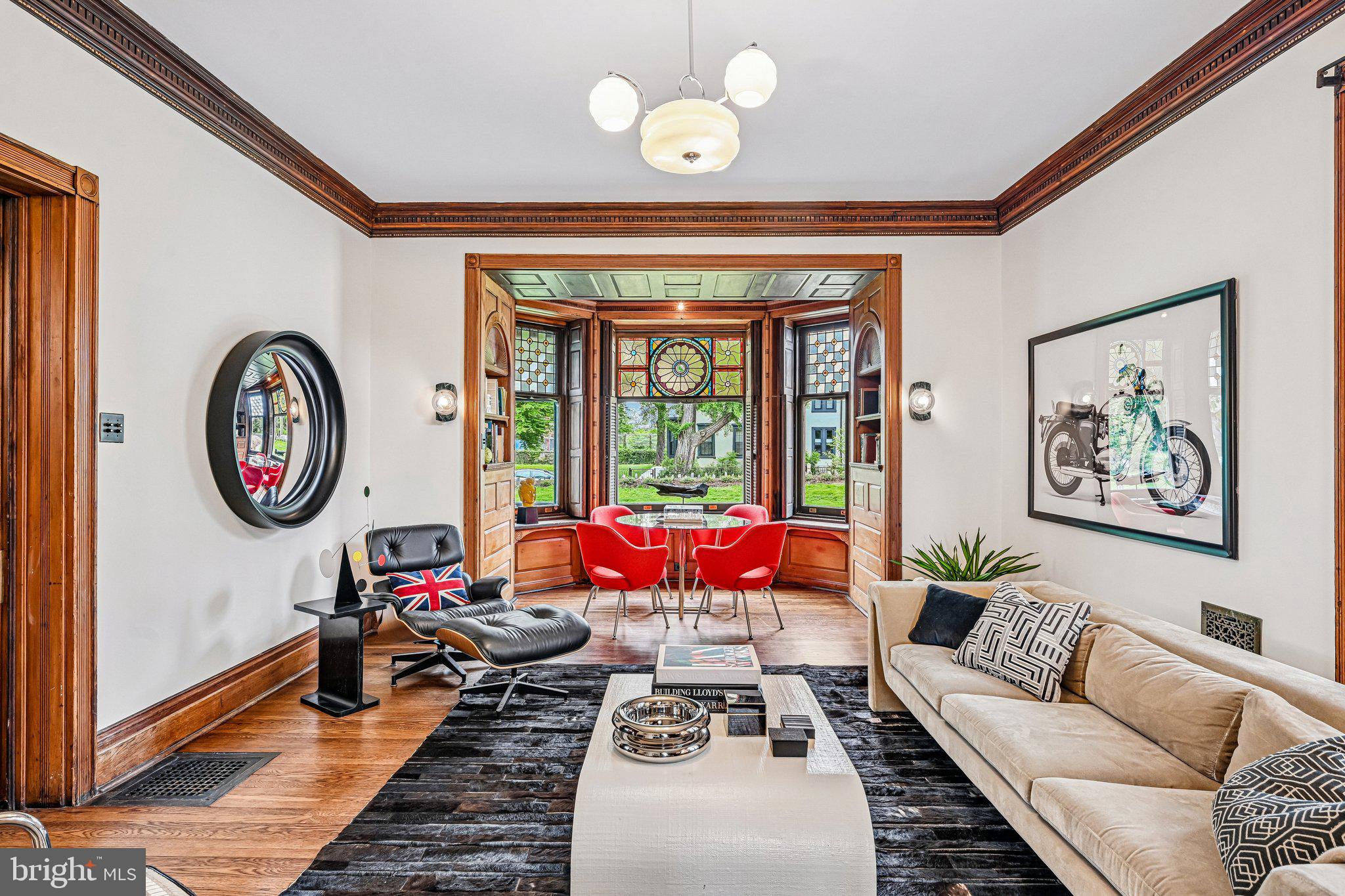 Occasionally, a home with truly one-of-a-kind architectural elements is thoughtfully reimagined with deep respect for its original character. Welcome to 51 E. Penn Street, a distinctive Germantown residence designed by George T. Pearson, offering a rare opportunity to own a historically significant property where celebrated stewardship has seamlessly united the craftsmanship of the past with the comforts and sophistication of modern living.

This extraordinary home stands apart for its preserved artistry and cohesive design narrative centered around sun and star motifs, woven throughout its leaded and stained glass, millwork, and architectural detailing. A dramatic entry sequence introduces the home’s exceptional craftsmanship with richly preserved woodwork, intricate paneling, and striking original stained glass.

The main living space features a dramatic bay window with leaded glass, built-in oak bookshelves, and an ornate fireplace with integrated millwork and decorative floral relief tile. French doors open to a large patio, creating a natural extension of the living space for quiet mornings or evening gatherings.

A formal dining room, currently styled as a den and reading room, offers a second fireplace framed by richly detailed embossed ceramic tile with an organic floral motif.

The original butler’s pantry, complete with its copper sink and preserved cabinetry, remains a beautifully intact reflection of the home’s historic craftsmanship. The fully renovated chef’s kitchen was thoughtfully designed for modern living and entertaining, featuring a large island topped with Arabescato marble and deVOL plumbing fixtures. The adjacent mudroom includes laundry, powder room, and access to an expansive elevated patio ideal for outdoor dining and entertaining.

Upstairs, the second floor offers a spacious primary suite with sitting area, walk-in closet, wood-burning fireplace, Juliet balcony, and a beautifully updated en-suite bath with a curbless glass-enclosed shower, soaking tub, and radiant heated floors.

A second bedroom with its own wood-burning fireplace, generous linen storage, and an additional full bath with a large glass-enclosed shower complete this level.

The third floor provides three additional bedrooms and another updated full bath, offering flexibility for guests, offices, or creative spaces.

Additional highlights include a two-car garage with extra off-street parking, two-zone central air, custom Indow interior window inserts, fully updated electrical systems, and new copper water service.

Ideally located just 0.2 miles from Germantown Friends School and Pomelo Flowers, 0.3 miles from SEPTA’s Wister Station, 1.1 miles from Weaver’s Way Co-op, and 1.6 miles from the Wissahickon trailhead.

With extraordinary millwork, original hardwood floors, irreplaceable stained glass, and thoughtfully executed upgrades throughout, 51 E. Penn Street represents a rare opportunity to own an architectural work of art- a home where history, design, and modern living exist in exceptional balance.