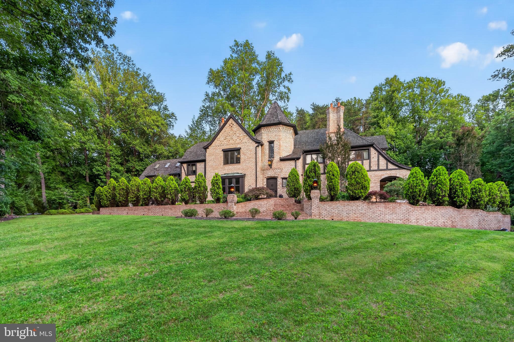 Welcome to Castlewood, an extraordinary 10,000-square-foot French Normandy Manor positioned on nearly two private acres bordering 7 acres of protected land. A true labor of historic artistry, the estate features structural steel I-beam engineering cloaked in the masterful brickwork of Archie Holleman and the legendary iron artistry of Danny Hurwitz, renowned for his restoration of the White House gates. Cross the threshold via a 200-pound artisan oak door into a breathtaking 40-foot soaring tower foyer anchored by a Gone with the Wind-inspired staircase and an authentic 1629 Lord Symington Fisk coat-of-arms. Rich hand-hewn woodwork, 250-year-old historic yellow pine floors, and grand yet inviting living spaces evoke the romance of classic English architecture, while proportions designed for modern living allow for effortless entertaining. Pass through 9-foot antique church pocket doors to discover a bespoke executive library crafted entirely from a single, select cherry tree with a walnut mantel matching the historic Georgetown Club.
Elite Amenities & Luxury Living Designed for the culinary enthusiast, the expansive kitchen showcases rich marble counters, custom cherry cabinetry, and antique brick accents. Descend the spiral staircase to a truly priceless wine cellar, featuring a brick floor reclaimed directly from the historic Gettysburg sidewalk where Abraham Lincoln delivered his address. The main-level wing hosts a sprawling master sanctuary boasting a fireplace, dual "his and her" bathrooms, and a body-massage jet shower with a heated seat. Luxury lifestyle features abound, including a billiards studio with a high-beamed ceiling, an authentic Finnish sauna custom-built from South African wood, and a multi-zone radiant heat system. Outside, a handmade brick veranda overlooks a botanical collector's dream—including 16 Japanese Maples and kitchen gardening beds—Community tennis and pickleball courts and miles of running and biking trails on the W&OD. More professional photos to come.