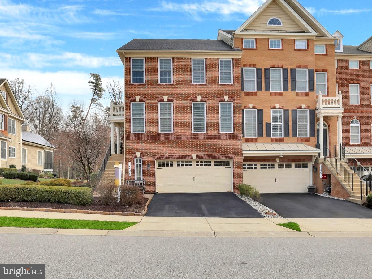 Welcome to 8507 Pine Springs Drive – a beautifully appointed end-unit townhome in the sought-after Arundel Forest community. With its stately brick front, elegant elevation, and front-loading garage, this former model home combines luxury, comfort, and smart design. The professionally landscaped exterior and spacious driveway create a warm and welcoming first impression. Step inside through the upgraded glass front door into a grand foyer adorned with gleaming hardwood floors, a neutral designer palette, and a statement chandelier that sets the tone for the rest of the home. To your right, the formal living room features elegant window treatments and custom lighting, while the formal dining room showcases detailed crown molding, classic sconces, and a sophisticated chandelier—ideal for hosting and entertaining. Continue into the spacious family room, where hardwood floors extend throughout, seamlessly connecting each space. Integrated speaker systems elevate the ambiance, and natural light pours in from the surrounding windows. The adjacent morning room is a showstopper with its coffered ceilings, three walls of windows, and tranquil views, creating the perfect space to relax or entertain. The gourmet kitchen is a chef’s dream—outfitted with stainless steel appliances, 42” custom cabinetry with crown molding, under-cabinet lighting, upgraded granite countertops, a dramatic herringbone marble backsplash, black hardware, and a deep farmhouse sink. Additional highlights include a wall oven with built-in microwave, a large walk-in pantry, a butler’s pantry, bar-height seating with pendant lighting, and a sunlit breakfast area with direct access to your private deck—perfect for morning coffee or evening unwinding. A stylish powder room with designer tile accent wall completes the main level. Upstairs, retreat to your luxurious primary suite featuring soaring cathedral ceilings, built-in speakers, and a generously sized walk-in closet with custom built-ins. The private sitting area is surrounded by windows on three sides, offering both serenity and natural light. The spa-inspired ensuite bath features a soaking tub, frameless glass walk-in shower with marble tile and bench seating, double granite vanities, upscale hardware, and a private water closet. Two additional bedrooms offer vaulted ceilings, designer window treatments, and generous closet space. A beautifully appointed hall bath with luxury tilework and an upper-level laundry area complete this level. The finished lower level is an entertainer’s haven, featuring a media wall with three built-in TVs, custom wood-paneled accent wall, built-in storage, a billiards space, and a bonus area perfect for an office or creative studio. Step outside to your fully fenced backyard retreat with a paver patio, built-in retaining wall, tranquil water fountain, additional storage shed, and lush landscaping—ideal for relaxing or entertaining in complete privacy. This energy-efficient smart home includes dual 92% efficient gas heating systems, a high-efficiency HVAC system, Nest programmable thermostat, Tyvek HomeWrap, Low-E dual-pane insulated windows, upgraded attic and wall insulation, air barrier and duct sealing, 2x6 exterior framing and an insulated steel garage door. A 35-year architectural roof adds even more value. Arundel Forest residents enjoy resort-style amenities including a clubhouse, fitness center, outdoor pool, gated playground, scenic trails, and picnic areas. Located just minutes from premier shopping and dining, with easy access to Fort Meade, Columbia, Baltimore, Washington D.C., BWI Airport, and Arundel Mills—this is luxury living at its finest.