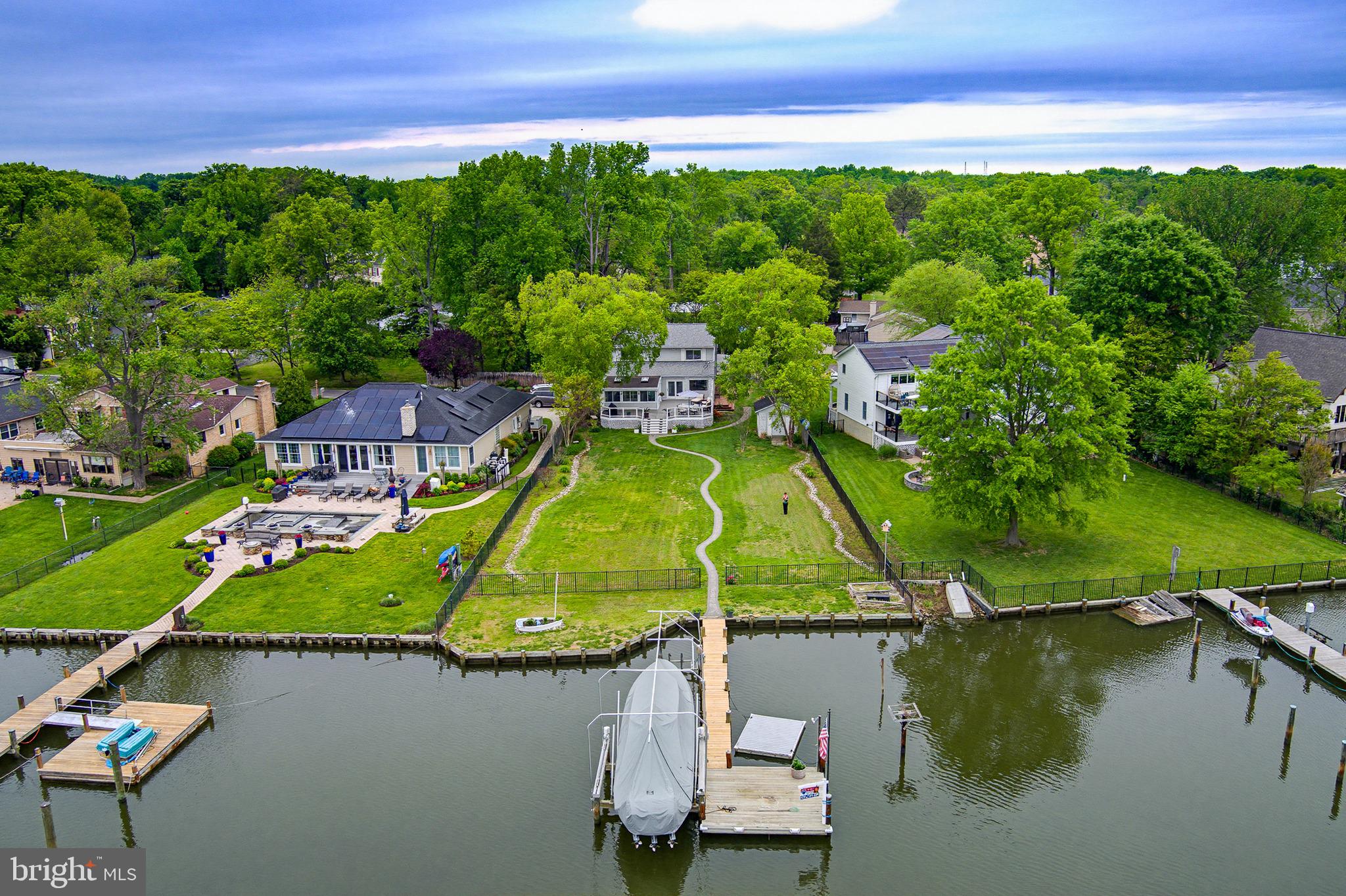 Enjoy approximately 5 ft water depth at your private pier on protected Whitemarsh Creek, off Rhode River—just a short boat ride to the Chesapeake Bay and all your favorite waterfront dining destinations! This property is built for both relaxation and entertaining, featuring a spacious TimberTech deck with stunning water views—perfect for hosting gatherings or enjoying peaceful evenings by the water. A 20,000 lb boat lift with remote makes boating effortless. Inside, you’ll find a flexible and inviting layout with: 2 bedrooms and 2 full baths on the main level, 3 additional bedrooms upstairs (one currently configured as an oversized walk-in closet—easily converted back), a very large owner’s suite with its own walk-in closet, a bright four-season room with a separate in-wall A/C unit and convenient dog door.  The half-acre lot at the end of the street offers exceptional privacy, complemented by a flat, fenced yard—ideal for pets, play, and outdoor enjoyment. A charming paver walkway leads to the waterfront, enhancing the home’s outdoor appeal. Seller updates include:  New Roof (2020), Two new high-efficiency heat pump systems, newer stainless steel appliances, including an induction stove, Updated flooring on main level, deck (2024),  W&D (2021), sump pump, and recently cleaned vents.  Opportunity knocks: The home offers a fantastic footprint for those looking to personalize and modernize. With great bones, waterfront location, and generous space, it’s the perfect canvas to create your dream home.   ✨Wraparound porch. Private setting. Boater’s lifestyle. Endless potential.