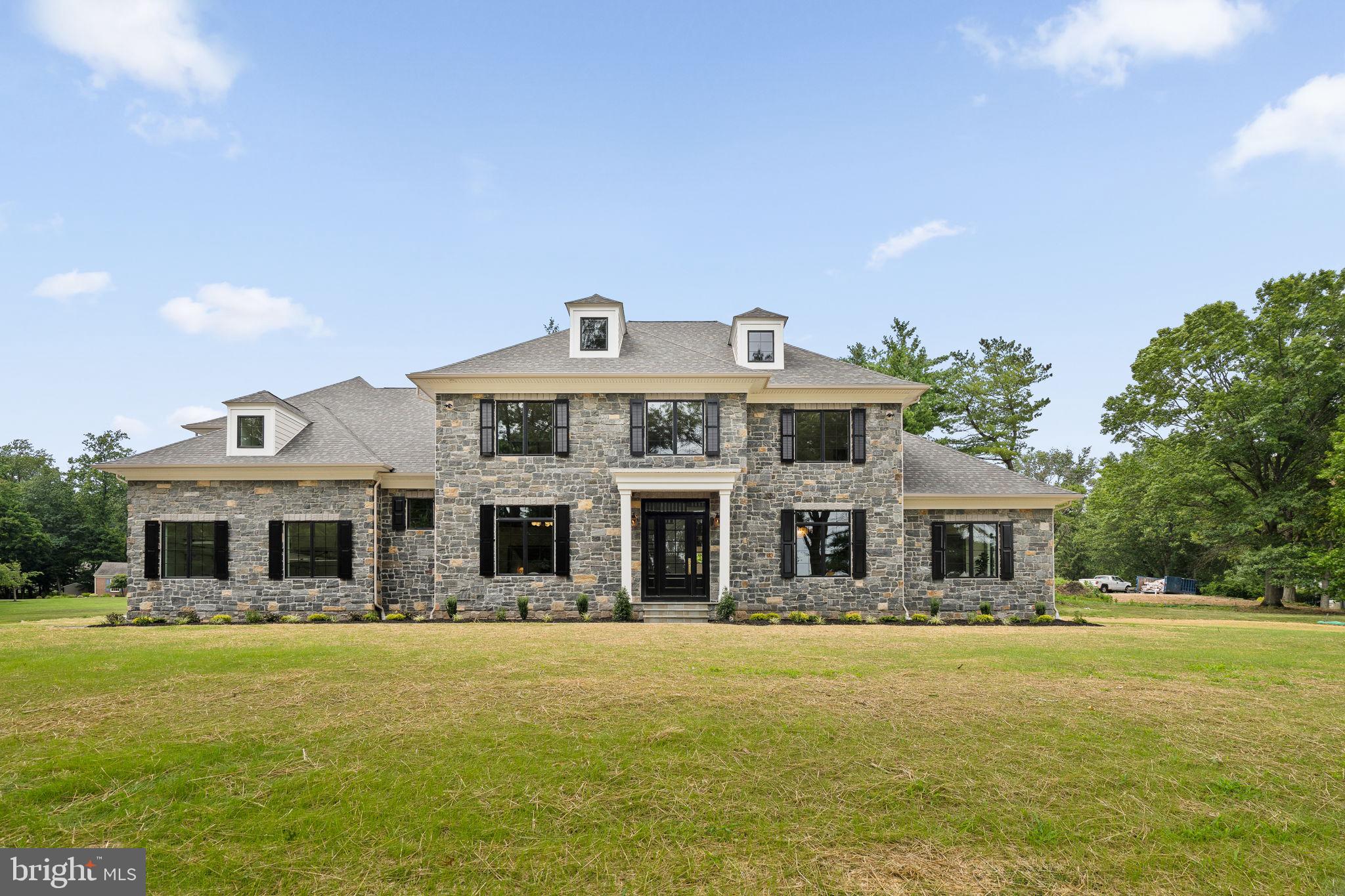 Welcome to 725 W. Curry Drive, Blue Bell, a one-of-a-kind custom-built luxury residence thoughtfully designed with timeless architecture, exceptional craftsmanship, and designer finishes throughout. This stunning new construction offers 5 spacious bedrooms, 6 full bathrooms, 1 powder room, and a beautifully finished basement, creating the perfect balance of elegance, comfort, and functionality.

A grand front elevation featuring a full natural stone façade, Andersen 400 Series black windows, gas lanterns, a bluestone paver walkway, and professionally crafted exterior millwork creates unforgettable curb appeal. Inside, you’ll be welcomed by soaring 10-foot ceilings, rich 5-inch solid white oak flooring, and a striking herringbone foyer that immediately sets the tone for the home’s refined design. Custom molding, extensive millwork, solid-core 8-foot doors, designer lighting, and premium finishes continue throughout every level.

The gourmet kitchen is designed to impress, featuring custom inset cabinetry with brass hardware, honed Carrara marble countertops with an elegant OG edge, a custom range hood, 42-inch ILVE range, 42-inch paneled Monogram refrigerator and an oversized butler’s pantry, creating an ideal space for both everyday living and entertaining.

The adjoining family room showcases exposed oak ceiling beams, custom built-in bookcases, and a stunning marble-surround gas fireplace. Additional gathering spaces include a sophisticated sitting room with a coffered ceiling, while the luxurious primary suite offers a beautifully detailed tray ceiling and a spa-inspired bath designed for everyday relaxation.

Every bedroom enjoys the privacy of an en-suite bathroom finished with designer tile and premium Kingston Brass plumbing fixtures, while Kohler fixtures and thoughtfully selected finishes reinforce the home’s exceptional quality throughout.

Designed for today’s lifestyle, the home also features a custom laundry room with inset white oak cabinetry, a functional mudroom with built-in bench seating and storage, a fully finished basement offering additional living and entertaining space, and a spacious three-car garage.
Outside, enjoy seamless indoor-outdoor living with a rear brick patio complete with a custom exterior fireplace—perfect for relaxing evenings or entertaining guests year-round.

Constructed with quality in mind, this exceptional home also includes a dual-zone Carrier HVAC system, 400-amp electrical service, CertainTeed architectural roofing, Hardie siding on the rear elevation, and numerous additional luxury upgrades throughout.

Perfectly situated in the heart of Blue Bell, 725 W. Curry Drive offers the rare opportunity to own a truly custom-built home where every detail has been carefully considered. This is luxury living at its finest.