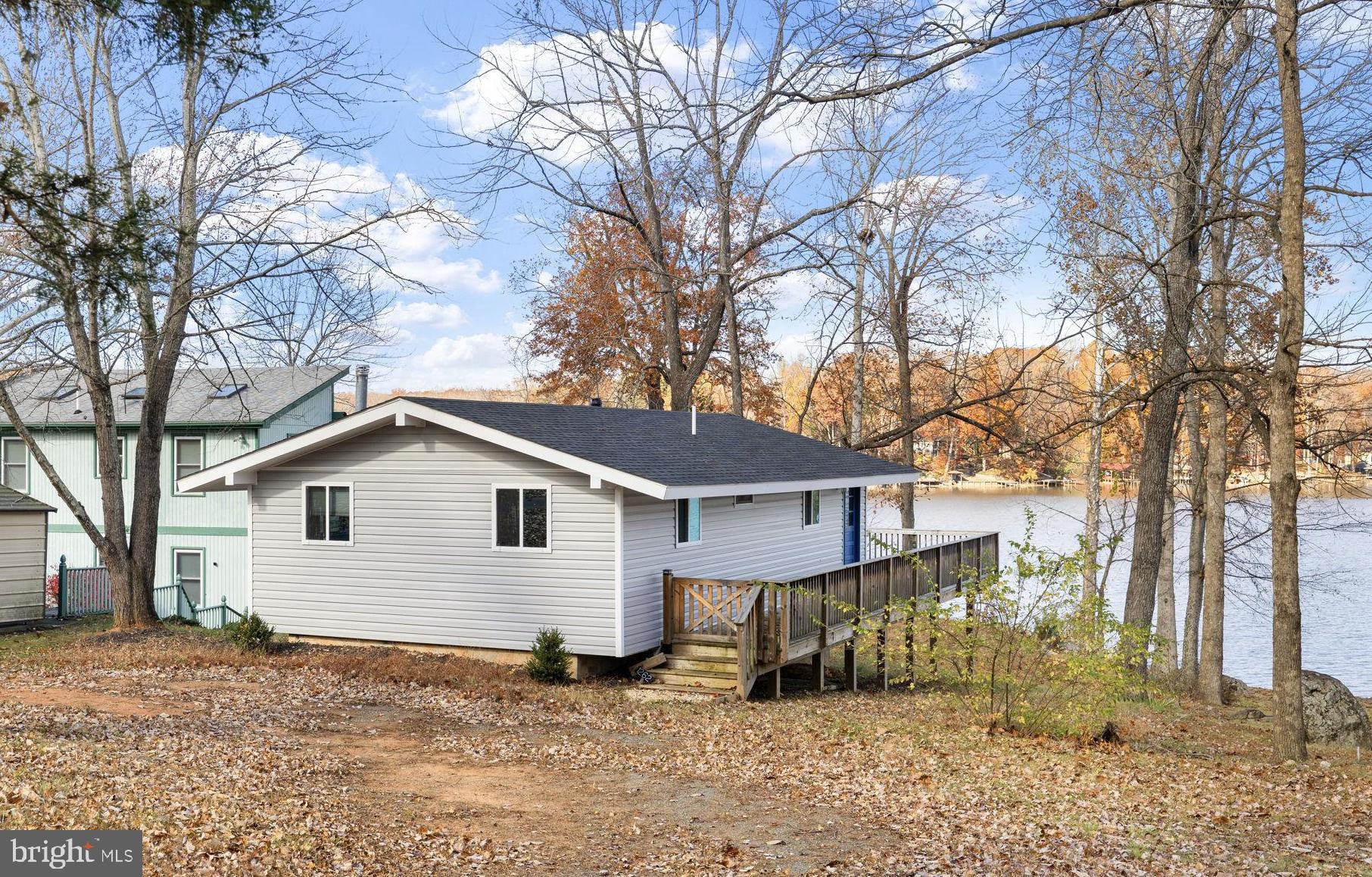 Your lake adventure starts here! An incredible value on this beautifully renovated chalet-style home that's all about fun, relaxation, and making lifelong memories. Tucked away in the gated community of Blue Ridge Shores on Lake Louisa, this charming retreat has a beautiful sandy shoreline with bulkhead, and your very own boat dock—just waiting for your next lake adventure! Step inside to stunning wide-open water views from the entire home that features 1,332 finished square feet spread across two levels. This 3 bedroom, 2 full bath home features an open floor plan with vaulted ceilings and a cozy wood-burning fireplace. The updated kitchen showcases white cabinetry, stainless steel appliances, and stunning butcher block counters, opening seamlessly to the family room—perfect for entertaining. The main level hosts two bedrooms and a full bath, while the finished walkout basement includes a family room, rec area, additional bedroom, full bath, and laundry. Fish off your dock, build sandcastles on the beach, or simply watch the sunset dance across the lake. You’ll love the community amenities—from beaches and boat docks to tennis and basketball courts, walking trails, and playgrounds. It’s a golf cart friendly neighborhood that keeps the fun rolling all year long. With high-speed Xfinity internet, you can even work from your lake house (if you must!). Conveniently located just 10 minutes from the town of Louisa, you’ll find great local dining, shopping, and groceries nearby. This home has been recently renovated and is ready for you to dive right into lake life! Come live where every day feels like vacation. Unplug, unwind, and let your stress drift away at this adorable waterfront retreat! Whether relaxing by the water or gathering around the fire, this is the lake retreat you’ve been waiting for!