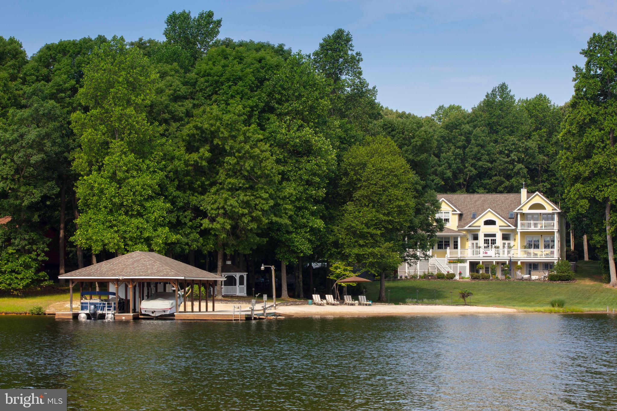 One of the most coveted and breathtaking waterfront estates ever offered at Lake Anna. Featured in Home & Design Magazine and professionally curated by one of the top designers in the DC/MD/VA region, this extraordinary residence sets an unmatched standard for luxury lakefront living. Perfectly positioned on a deep, wide no-wake cove on the exclusive private side of Lake Anna, this awe-inspiring property has been meticulously renovated with the highest level of craftsmanship and design. Offering over 5,600 finished square feet, the home features 6 bedrooms, 5 full bathrooms, and a dedicated office or hobby room—an exceptional blend of architectural elegance, thoughtful amenities, and sweeping water views. The interior opens with a grand foyer that flows effortlessly into the great room, dining area, and gourmet kitchen. Designed for both everyday living and elevated entertaining, the kitchen is outfitted with Wi-Fi–enabled Sub-Zero and Wolf appliances, double wall ovens with warming drawer, induction cooktop with telescoping vent, 2" Italian marble countertops, statement pendant lighting, and an oversized island. A walk-in pantry with custom shelving and motion-activated lighting complements a Sub-Zero beverage center featuring two refrigeration drawers and a humidor capable of storing up to 86 bottles. The great room impresses with vaulted ceilings, custom black millwork surrounding the wood burning pellet stove fireplace, and elegant built-in cabinetry. The primary suite is a private retreat, offering its own covered balcony overlooking the lake and ensuite with freestanding tub, dual vanities, tiled shower, and private water closet. Two additional upper-level bedrooms each include their own full bath. The finished walk-out lower level is ideal for relaxing and entertaining, featuring a family room with recreation space, a custom bar, two bedrooms connected by a Jack-and-Jill bath, a utility/storage room with a second Sub-Zero refrigerator/freezer, and access to the built-in garage. Every detail has been carefully considered, including stunning high-end wallpaper and designer lighting, a whole-house Sonos audio system, Moen Flo smart water monitoring with leak detection and automatic alerts, and the ability to remotely turn the water on or off from your phone. The Nest fire and carbon monoxide system, Philips Hue lighting, and smart home features are all conveniently app-controlled, offering peace of mind and effortless control whether you’re at the lake or miles away. Additional upgrades include Nest thermostats, dual-zone HVAC, two water heaters, whole-house water filtration, marble bathrooms, high-speed fiber internet at both the home and boathouse, whole-house fan, and a 50-year architectural roof on both the home and boathouse (installed in 2019). Outdoors, enjoy expansive decks and patios overlooking the water, a manicured lawn, and a private sandy beach perfect for play and relaxation. Recreational amenities include a private basketball court (pickleball size) and, at the water’s edge, a stunning boathouse with composite decking, two covered slips with electric lifts, two jet ski lifts, a spacious sun deck, and two storage rooms for all your lake toys. With over 170 feet of shoreline, this property is perfectly designed for both peaceful retreat and unforgettable entertaining. Additional highlights include an outdoor shower, hot tub, fire pit, screened gazebo with electric, large paved driveway, extensive hardscaping, 12-zone Hunter lake-fed irrigation system, drip irrigation for hanging plants, and an invisible fence for pets. Recognized by Fox Business as the #1 “beach” vacation investment location in the nation, Lake Anna offers not only an unparalleled lifestyle but an exceptional investment opportunity. Located just two hours from Washington, D.C., this remarkable estate delivers the very best of luxury waterfront living.