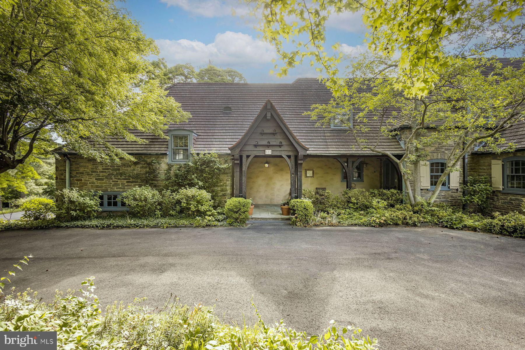 Welcome to 500 Telner Street, one of the finest Woodward houses in Chestnut Hill. Built in 1957, but resembling a 1925 house typical of the aesthetics of Chestnut Hill, this lovely estate was custom built for George Woodward, Jr. and his wife Harriet for their personal home. The Woodward family is well-known for building Chestnut Hill’s most charming estates. Its park-like setting and charming dovecote gracing the front entrance, surrounded by pink azaleas in Spring, make this fairy tale “cottage” come to life. This is one of the rare homes directly on Wissahickon Valley Park. Timeless charm, so typical in Woodward architecture, is brought to its zenith in this stone home, custom built to plans now archived at the Chestnut Hill Conservancy, with seemingly no expense spared. All the modern amenities you love, such as central air, a full 2 car garage, an attached separate apartment with its own private entrance, 5 full and 3 half baths (each bedroom and apartment with their own full bath), and enormous closets and attic space, offer comfort and convenience. With 8 inch deep granite window sills due to the thick walls, the house is exceptionally quiet due to the insulation, solid doors and stucco walls. Uniquely, the primary bedroom suite occupies an entire wing on the ground floor and features a spacious bath with dual bathrooms, each with its own shower or tub. The generous bedroom includes French doors opening to a private patio, a marble fireplace, built-in dresser, and separate closets, along with an adjoining sitting room with an additional marble fireplace. This wing creates total privacy from the other living spaces in the house. The grand living room, with an open floor plan connecting to the dining room, boasts 5 sets of French doors that are lit with morning sun, with an unobscured view filled with trees as it overlooks Cresheim Valley. Since 2013, multiple improvements have been made, including a new main kitchen with radiant floor heating, a Miele dish washer, Viking stove, convection oven, and a generous pantry complete with a cozy, sunny home office. The kitchen in the apartment is also new, with granite countertops, gas range and dishwasher, and added in 2020, a spacious southern exposure insulated glass addition opens out from the living room for your hot tub, 4 season relaxation and plant cultivation or display. A kitchenette is also located here. The circular and garage access driveways were repaved in 2023. The generous studio apartment has a separate entrance and contains multiple windows, a full bath and ample closets. The second floor contains 3 bedrooms and luxuriously, one full bath for each bedroom. Adding to the home's flexible layout is the possibility of complete separation of upstairs and downstairs due to the private entrance access to both the upstairs and the apartment. A large slate floor foyer at the front door absorbs all the comings and goings and stands the test of time. Located over the furnace room, the slate remains warm all winter long. A massive “playroom” in the finished basement, complete with fireplace, could be an exercise space, a guest bedroom (it has a large window), office, child or party space. While laundry is conveniently located on the ground floor, there is plumbing here in a large closet for another laundry facility. There is also a half bath in the basement and a very generous workshop space as well. An additional finished room which, at the owner’s option, could be reserved for the resident of the apartment to enlarge its capacity, or kept as part of the main residence.