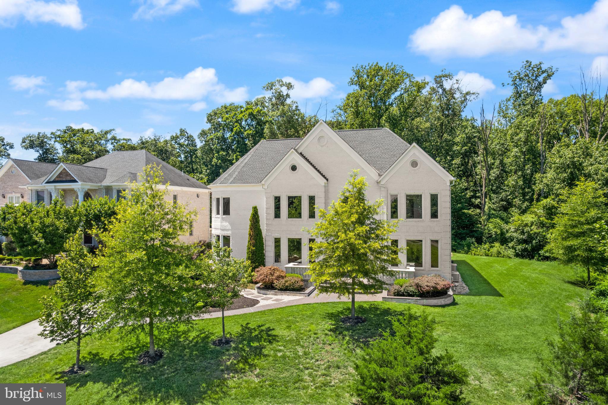 A glass-and-light modern masterpiece, this custom residence by Potomac Custom Homes spans nearly 10,000 finished square feet on a quiet cul-de-sac in The Reserves at Pinecrest, privately backing to protected Fairfax County parkland. Expansive walls of glass and dramatic vertical spaces set an unforgettable tone, anchored by soaring 20-ft ceilings in the main living area and the primary sitting room, with 10-ft ceilings throughout the rest of the home. A custom floating staircase wrapped in fully enclosed glass railings rises through every level, while large-format Roberto Cavalli porcelain flooring and radiant heat bring warmth and cohesion to the main living spaces.

At the heart of the home, a chef's kitchen is designed to impress: custom Italian UNICA cabinetry, 3-inch DEKTON Aura waterfall countertops, a professional GE Monogram appliance suite with induction range, and an expansive island built for gathering. GROHE designer fixtures and copper supply lines reflect a commitment to quality throughout.

Designed for entertaining and everyday escape, the finished lower level delivers a dedicated home theater, a golf simulator room with an $80K build-out, and a private gym, with theater seating, projector and screen, and gym equipment all conveying.

Outdoor living rivals a private resort. A saltwater fiberglass pool with Pentair heating, LED lighting, a decorative waterfall, and an automatic cover is surrounded by an expansive patio with a built-in Weber gas grill, outdoor refrigerator, and integrated storage. Upstairs, the primary suite opens to a private balcony retreat with a hot tub overlooking the trees.

Smart and built to last, the home features Control4 whole-home automation, a hardwired security system, a full-house Generac backup generator, three-zone Carrier HVAC, and app-controlled Rachio smart irrigation. A spacious 4-car garage with 8-ft doors, epoxy floors, and custom storage, plus a mudroom with a built-in pet-washing station, complete the offering.

Minutes to I-495, I-395, Route 236, Route 7, and Braddock Road, with parks, golf courses, shopping, and dining close by, this is contemporary luxury with a true sense of retreat in the heart of Northern Virginia.
